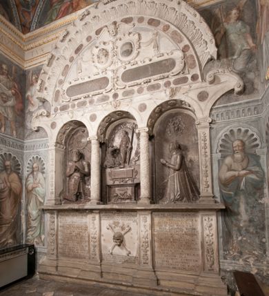 Zdjęcie nr 1: Nagrobek Grzegorza i Katarzyny Branickich znajduje się w kaplicy rodowej pod wezwaniem Najświętszej Marii Panny, na ścianie południowej, naprzeciwko wejścia. Składa się z trójosiowego cokołu i potrójnej filarowo-kolumnowej arkady z klęczącymi postaciami zmarłych po bokach adorujących znajdującą się pośrodku scenę ze zmartwychwstałym Chrystusem ukazującym się niewiernemu Tomaszowi. Całość wieńczy półkolista arkada z herbami Gryf i Kotwicz i tablicami inskrypcyjnymi. 
Dolna część artykułowa lizenami ozdobionymi motywami kandelabrowymi. W polu środkowym czaszka ze skrzyżowanymi piszczelami z inskrypcją w górnej i dolnej części: „POWIEDZ SVIETA [M]ADROSCI IESLI ZE SMIERC ZIWA / CZI MARTWA IESLI MARTWA CZEMV ZIWĄ BIWA / MALOWANA A IESLI ZIWA SMIERCIĄ CZEMV / ZOWIĄ IĄ NAD TO ZYWOT PRZECZ BIERZE KOZI/DEMV / TA IEST NA TWE PITANIE ODPOWIEC PRAWDZIWA / GDI TI ZYESZ SMIERC MARTVA GDY VMIERAS ZIWA / A IESLI ZLA CZI DOBRA CHCZES WIEDZIEC LI O TYM / IAKIS SĄM TAKĄ SMIELE SMIERC MIEĆ BĘDZIESZ PO TYM”. Na lewym polu inskrypcja „CO ZA DZIW ZEM POPIOLEM / WIEDZCIE ZESCIE WY / IAKO IA TENZE POPIOL, TO / IEDNO ZE ZYWY / BO GDIM SIĘ W PROCH ROSSIPAL / DOPIROM PRAWDZIWIE DOSZEDL, ZE CZLOWIEK TYMZE / PROCHEM CHOCIA ZYWIE / PATRZ ZE ZYWY POPIELIE A / TO POMNI SOBIE / ZES NA SWIECIE POPIOLEM / POPIOLEM I W GROBIE / A ZASZ NIEWIES CZYMEM BYL / A TERAZEM IAKI / OGLIANDAI, VWAZAIACZ ZE / SAM BEDZIESZ TAKI / BYLEM TERAS MIE NIE MASZ / IAK BIM TISZ NA SWIECIE / NIE BYL WY DZIS IESTESCIE / IUTRO NIEBEDZIECIE”. W polu cokołu „KTO TV LEZY POBOZNOSC / CNOTA OBYCZAIE / IAKICH NIERYCHLO VIZRĄ / BLISKO LEGLE KRAIE / IAKOSZ IE TAK MALY KĄT / MOGL ZACHOWAC W SOBIE / CZOSZ ALBO CNOTI LVCZKIE / GRZEBIĄ SCZIALEM W GROBIE / TILKOC TV CIALO LIEZY LIECZ / DVSZA W PRZESTRONE / NIEBIESKIE GMACHI WESŁA / KĘDI NIEZLICZONE / LATA POWIEDZIE. CZEMV IZE / MATKĄ BYLA / NIERZKAC POTOMSTWV ALIE / I SIROTOM SILA / TAKCI ZYWOT ZYWOTEM BYWA ZAKVPIONY / DOBRI FRIMARK DAC PLOCHI / ZA ON NIESKONCZONY”. Cokół zamyka wąski, silnie wysunięty gzyms z kimationem jońskim.
Trójosiowy podział nagrobka jest zachowany w partii środkowej, składającej się z trzech arkadowych wnęk, z których środkowa ujęta jest wolnostojącymi kolumnami jońskimi pokrytymi spiralnie ułożonymi pasami z motywem wici roślinnej, a sąsiednie od zewnątrz flankowane filarami pokrytymi motywami kandelabrowymi. W niezbyt głębokich niszach, których podniebienia zdobią kasetony z rozetami w kluczach uskrzydlone główki aniołków umieszczono wykonane w marmurze pińczowskim płaskorzeźby Chrystusa Zmartwychwstałego i adorujących go zmarłych, Grzegorza i Katarzynę Branickich. 
Zbawiciel jest ujęty całopostaciowo, frontalnie, w niewielkim wykroku, z głową zwróconą lekko do klęczącego po prawej stronie św. Tomasza. Jego ciało jest smukłe, wąskie w ramionach, z zaznaczonymi żebrami i mięśniami, osłonięte przewiązaną na biodrach szatą i płaszczem na lewym ramieniu. Chrystus ma pociągłą twarz, o wysokim czole, szerokich kościach policzkowych, wydatnym nosie i z głębokimi oczodołami. Przedstawiony został z długimi wąsami i brodą oraz opadającymi na ramiona, kręconymi włosami. W lewej ręce trzyma chorągiew i podtrzymuje szatę, a prawą rękę ma opuszczoną ku dołowi. 
Święty Tomasz ukazany jest z profilu, w szacie podwójnie przewiązanej w pasie sznurem i przerzuconym przez lewe ramie płaszczem. Twarz z brodą i długimi włosami, odwrócona w stronę Chrystusa. Do góry unosi również prawą rękę, zachowaną tylko do łokcia, lewą rękę trzyma ponad pasem. Figura mężczyzny wyrzeźbiona w kamieniu, polichromowana, przysłania wieniec z obłoków i uskrzydlonych głów puttów otaczający Chrystusa. 
Postacie stoją na podwójnym postumencie. W jego górnej części wyryto sentencję łacińską na prostokątnej tablicy umieszczonej w ozdobnym kartuszu, z zawiniętym spiralnie wycięciem krawędzi górnej i z dodaną w krawędzi dolnej główką uskrzydlonego putta. Napis na postumencie: „PER QVEM ET NOS / RESVRGERE DEVOTA / MENTE, CREDIMVS”. Na płycie poniżej płaskorzeźbione, leżące na prawym boku putto podpierające głowę na prawej ręce, natomiast w lewej trzymające klepsydrę. Nagie ciało, lekko przysłonięte draperią, spoczywa na poduszce z dwoma pomponami. Prawa noga jest wyprostowana, lewa zgięta w kolanie. Twarz pucołowata, z otwartymi oczami, otoczona gęstymi puklami loków. Przed dzieckiem leży czaszka. Nad nim znajduje się grawerowany kartusz z napisem: „HODIE MIHI / CRAS TIBI”. 
W arkadzie po lewej stronie przedstawiony został w trzech czwartych, zwrócony ramionami do widza Grzegorz Branicki. Postać klęczy na poduszce, szerokie dłonie złożone ma razem na piersiach, a głowę lekko uniesioną. Twarz Branickiego o pociągłych rysach, szerokich kościach policzkowych i dużych oczach, z wysokim czołem przysłoniętym zaczesanymi do przodu włosami. Ukazany z wąsami i długą, pofalowaną brodą. Ubrany jest w pełną, dekorowaną zbroję, spod której wystaje jaka i nogawice. Na szyi zawieszony łańcuch, a u stóp ostrogi. Przy nogach Branickiego leżą rękawice i hełm z trzema piórami. Nad głową wznoszą się panoplia, złożone z okrągłej tarczy i skrzyżowanych miecza, szabli, buławy, łuku, kołczanu ze strzałami i włóczni.
Po lewej stronie arkadę wypełnia ujęta z profilu, postać klęczącej na dwóch kolanach Katarzyny Branickiej. Jest ubrana w długą szubę, opadającą sztywnymi, rozchodzącymi się fałdami, u dołu załamującymi się, które zasłaniają sylwetkę. Na głowie ma czepiec przysłaniający włosy i podwikę. Twarz o łagodnych rysach, z długim nosem, małymi ustami i lekko zadartym podbródkiem. Ręce złożone razem na piersiach. Na palcach wskazującym i serdecznym lewej dłoni pierścienie, a ponad nadgarstkiem czterokrotnie nawinięty różaniec. Ponad figurą płaskorzeźbione tondo z Matką Boską z Dzieciątkiem otoczonymi wieńcem obłoków. Maria siedzi, ubrana w długą suknię, z welonem na głowie, z płaszczem zarzuconym na ramiona, którym lekko okrywa nagie Dzieciątko.
Zwieńczenie nagrobka o brzegach inkrustowanych marmurowymi kołami i elipsami, ujęte ornamentalnymi uszami, jest zakończone pasem z zawijającymi się do środkami kartuszami i równolegle ułożonymi liśćmi akantu. Tympanon wypełnia dekoracja złożona z czterech kartuszy: dwóch owalnych na tle paludamentu, zwieńczonych uskrzydloną główką anioła z godłami herbów Gryf i Kotwicz i dwóch podłużnych z inskrypcjami. Na tablicy po lewej stronie inskrypcja: „MAGNIFICO D(OMI)NO GREGORIO A RUSCA BRANICZKI OLIM VENA/TORI ET BURGRABIO CRAC(OVIENSI) CAPITANEO NIEPOŁOMIECEN(SI) VIRO / INTEGERRIMO DE REGIBVS SVIS ET RE PVB(LICA) BENE MERITO RELIGIO/NIS CATHOLICE AMANTISSIMO AMICIS FIDELISSIMO, OMNIBVS AFFABI/LI ET BENIGNO JOANNES A RUSCA BRANICZKI VENATOR CRACO(VIENSIS) CAPITANEVS NIEPOŁOMICEN(SI) MESTVS FILIUS PARENTI CHA/RISSIMO POSVIT OBYT 9 MAII A(NNO) D(OMINI) 1595 AETATIS SUE 60”. Napis wykuty po prawej stronie: “MAGNIFICAE D(OMI)NE CATHARINAE MAGNIFICI OLIM D(OMI)NI AUGUSTINI / KOTFICZ D(OMINI) SIGISMVNDI I POLONIAE REGIS STABVLI PREFECTI / VEXILIFERISQUE CURIE ET BURGRABY CRACO(VIENSIS) FILIE MATRONAE / LECTISSIME QVE CVM PVDORE ET MORVM MIRA ELEGANTIA / MARITI SUMMUM AMOREM VIRTUTE ET MODESTIA OMNIVM BENE/VOLENTIAM MERVISSET ACERBISSIMA MORTE AB OCVLIS EREPTA EST / IDEM FILIUS MATRI AMANTISSIME CVM LACRIMIS POSVIT. OBYT / 8 OCTOBRIS A(NNO) D)OMINI) 1588 AETATIS SUE 38". 
