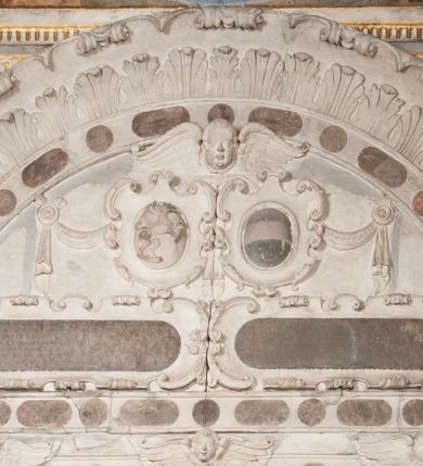 Zdjęcie nr 4: Nagrobek Grzegorza i Katarzyny Branickich znajduje się w kaplicy rodowej pod wezwaniem Najświętszej Marii Panny, na ścianie południowej, naprzeciwko wejścia. Składa się z trójosiowego cokołu i potrójnej filarowo-kolumnowej arkady z klęczącymi postaciami zmarłych po bokach adorujących znajdującą się pośrodku scenę ze zmartwychwstałym Chrystusem ukazującym się niewiernemu Tomaszowi. Całość wieńczy półkolista arkada z herbami Gryf i Kotwicz i tablicami inskrypcyjnymi. 
Dolna część artykułowa lizenami ozdobionymi motywami kandelabrowymi. W polu środkowym czaszka ze skrzyżowanymi piszczelami z inskrypcją w górnej i dolnej części: „POWIEDZ SVIETA [M]ADROSCI IESLI ZE SMIERC ZIWA / CZI MARTWA IESLI MARTWA CZEMV ZIWĄ BIWA / MALOWANA A IESLI ZIWA SMIERCIĄ CZEMV / ZOWIĄ IĄ NAD TO ZYWOT PRZECZ BIERZE KOZI/DEMV / TA IEST NA TWE PITANIE ODPOWIEC PRAWDZIWA / GDI TI ZYESZ SMIERC MARTVA GDY VMIERAS ZIWA / A IESLI ZLA CZI DOBRA CHCZES WIEDZIEC LI O TYM / IAKIS SĄM TAKĄ SMIELE SMIERC MIEĆ BĘDZIESZ PO TYM”. Na lewym polu inskrypcja „CO ZA DZIW ZEM POPIOLEM / WIEDZCIE ZESCIE WY / IAKO IA TENZE POPIOL, TO / IEDNO ZE ZYWY / BO GDIM SIĘ W PROCH ROSSIPAL / DOPIROM PRAWDZIWIE DOSZEDL, ZE CZLOWIEK TYMZE / PROCHEM CHOCIA ZYWIE / PATRZ ZE ZYWY POPIELIE A / TO POMNI SOBIE / ZES NA SWIECIE POPIOLEM / POPIOLEM I W GROBIE / A ZASZ NIEWIES CZYMEM BYL / A TERAZEM IAKI / OGLIANDAI, VWAZAIACZ ZE / SAM BEDZIESZ TAKI / BYLEM TERAS MIE NIE MASZ / IAK BIM TISZ NA SWIECIE / NIE BYL WY DZIS IESTESCIE / IUTRO NIEBEDZIECIE”. W polu cokołu „KTO TV LEZY POBOZNOSC / CNOTA OBYCZAIE / IAKICH NIERYCHLO VIZRĄ / BLISKO LEGLE KRAIE / IAKOSZ IE TAK MALY KĄT / MOGL ZACHOWAC W SOBIE / CZOSZ ALBO CNOTI LVCZKIE / GRZEBIĄ SCZIALEM W GROBIE / TILKOC TV CIALO LIEZY LIECZ / DVSZA W PRZESTRONE / NIEBIESKIE GMACHI WESŁA / KĘDI NIEZLICZONE / LATA POWIEDZIE. CZEMV IZE / MATKĄ BYLA / NIERZKAC POTOMSTWV ALIE / I SIROTOM SILA / TAKCI ZYWOT ZYWOTEM BYWA ZAKVPIONY / DOBRI FRIMARK DAC PLOCHI / ZA ON NIESKONCZONY”. Cokół zamyka wąski, silnie wysunięty gzyms z kimationem jońskim.
Trójosiowy podział nagrobka jest zachowany w partii środkowej, składającej się z trzech arkadowych wnęk, z których środkowa ujęta jest wolnostojącymi kolumnami jońskimi pokrytymi spiralnie ułożonymi pasami z motywem wici roślinnej, a sąsiednie od zewnątrz flankowane filarami pokrytymi motywami kandelabrowymi. W niezbyt głębokich niszach, których podniebienia zdobią kasetony z rozetami w kluczach uskrzydlone główki aniołków umieszczono wykonane w marmurze pińczowskim płaskorzeźby Chrystusa Zmartwychwstałego i adorujących go zmarłych, Grzegorza i Katarzynę Branickich. 
Zbawiciel jest ujęty całopostaciowo, frontalnie, w niewielkim wykroku, z głową zwróconą lekko do klęczącego po prawej stronie św. Tomasza. Jego ciało jest smukłe, wąskie w ramionach, z zaznaczonymi żebrami i mięśniami, osłonięte przewiązaną na biodrach szatą i płaszczem na lewym ramieniu. Chrystus ma pociągłą twarz, o wysokim czole, szerokich kościach policzkowych, wydatnym nosie i z głębokimi oczodołami. Przedstawiony został z długimi wąsami i brodą oraz opadającymi na ramiona, kręconymi włosami. W lewej ręce trzyma chorągiew i podtrzymuje szatę, a prawą rękę ma opuszczoną ku dołowi. 
Święty Tomasz ukazany jest z profilu, w szacie podwójnie przewiązanej w pasie sznurem i przerzuconym przez lewe ramie płaszczem. Twarz z brodą i długimi włosami, odwrócona w stronę Chrystusa. Do góry unosi również prawą rękę, zachowaną tylko do łokcia, lewą rękę trzyma ponad pasem. Figura mężczyzny wyrzeźbiona w kamieniu, polichromowana, przysłania wieniec z obłoków i uskrzydlonych głów puttów otaczający Chrystusa. 
Postacie stoją na podwójnym postumencie. W jego górnej części wyryto sentencję łacińską na prostokątnej tablicy umieszczonej w ozdobnym kartuszu, z zawiniętym spiralnie wycięciem krawędzi górnej i z dodaną w krawędzi dolnej główką uskrzydlonego putta. Napis na postumencie: „PER QVEM ET NOS / RESVRGERE DEVOTA / MENTE, CREDIMVS”. Na płycie poniżej płaskorzeźbione, leżące na prawym boku putto podpierające głowę na prawej ręce, natomiast w lewej trzymające klepsydrę. Nagie ciało, lekko przysłonięte draperią, spoczywa na poduszce z dwoma pomponami. Prawa noga jest wyprostowana, lewa zgięta w kolanie. Twarz pucołowata, z otwartymi oczami, otoczona gęstymi puklami loków. Przed dzieckiem leży czaszka. Nad nim znajduje się grawerowany kartusz z napisem: „HODIE MIHI / CRAS TIBI”. 
W arkadzie po lewej stronie przedstawiony został w trzech czwartych, zwrócony ramionami do widza Grzegorz Branicki. Postać klęczy na poduszce, szerokie dłonie złożone ma razem na piersiach, a głowę lekko uniesioną. Twarz Branickiego o pociągłych rysach, szerokich kościach policzkowych i dużych oczach, z wysokim czołem przysłoniętym zaczesanymi do przodu włosami. Ukazany z wąsami i długą, pofalowaną brodą. Ubrany jest w pełną, dekorowaną zbroję, spod której wystaje jaka i nogawice. Na szyi zawieszony łańcuch, a u stóp ostrogi. Przy nogach Branickiego leżą rękawice i hełm z trzema piórami. Nad głową wznoszą się panoplia, złożone z okrągłej tarczy i skrzyżowanych miecza, szabli, buławy, łuku, kołczanu ze strzałami i włóczni.
Po lewej stronie arkadę wypełnia ujęta z profilu, postać klęczącej na dwóch kolanach Katarzyny Branickiej. Jest ubrana w długą szubę, opadającą sztywnymi, rozchodzącymi się fałdami, u dołu załamującymi się, które zasłaniają sylwetkę. Na głowie ma czepiec przysłaniający włosy i podwikę. Twarz o łagodnych rysach, z długim nosem, małymi ustami i lekko zadartym podbródkiem. Ręce złożone razem na piersiach. Na palcach wskazującym i serdecznym lewej dłoni pierścienie, a ponad nadgarstkiem czterokrotnie nawinięty różaniec. Ponad figurą płaskorzeźbione tondo z Matką Boską z Dzieciątkiem otoczonymi wieńcem obłoków. Maria siedzi, ubrana w długą suknię, z welonem na głowie, z płaszczem zarzuconym na ramiona, którym lekko okrywa nagie Dzieciątko.
Zwieńczenie nagrobka o brzegach inkrustowanych marmurowymi kołami i elipsami, ujęte ornamentalnymi uszami, jest zakończone pasem z zawijającymi się do środkami kartuszami i równolegle ułożonymi liśćmi akantu. Tympanon wypełnia dekoracja złożona z czterech kartuszy: dwóch owalnych na tle paludamentu, zwieńczonych uskrzydloną główką anioła z godłami herbów Gryf i Kotwicz i dwóch podłużnych z inskrypcjami. Na tablicy po lewej stronie inskrypcja: „MAGNIFICO D(OMI)NO GREGORIO A RUSCA BRANICZKI OLIM VENA/TORI ET BURGRABIO CRAC(OVIENSI) CAPITANEO NIEPOŁOMIECEN(SI) VIRO / INTEGERRIMO DE REGIBVS SVIS ET RE PVB(LICA) BENE MERITO RELIGIO/NIS CATHOLICE AMANTISSIMO AMICIS FIDELISSIMO, OMNIBVS AFFABI/LI ET BENIGNO JOANNES A RUSCA BRANICZKI VENATOR CRACO(VIENSIS) CAPITANEVS NIEPOŁOMICEN(SI) MESTVS FILIUS PARENTI CHA/RISSIMO POSVIT OBYT 9 MAII A(NNO) D(OMINI) 1595 AETATIS SUE 60”. Napis wykuty po prawej stronie: “MAGNIFICAE D(OMI)NE CATHARINAE MAGNIFICI OLIM D(OMI)NI AUGUSTINI / KOTFICZ D(OMINI) SIGISMVNDI I POLONIAE REGIS STABVLI PREFECTI / VEXILIFERISQUE CURIE ET BURGRABY CRACO(VIENSIS) FILIE MATRONAE / LECTISSIME QVE CVM PVDORE ET MORVM MIRA ELEGANTIA / MARITI SUMMUM AMOREM VIRTUTE ET MODESTIA OMNIVM BENE/VOLENTIAM MERVISSET ACERBISSIMA MORTE AB OCVLIS EREPTA EST / IDEM FILIUS MATRI AMANTISSIME CVM LACRIMIS POSVIT. OBYT / 8 OCTOBRIS A(NNO) D)OMINI) 1588 AETATIS SUE 38&quot;. 
