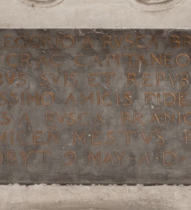 Zdjęcie nr 148: Nagrobek Grzegorza i Katarzyny Branickich znajduje się w kaplicy rodowej pod wezwaniem Najświętszej Marii Panny, na ścianie południowej, naprzeciwko wejścia. Składa się z trójosiowego cokołu i potrójnej filarowo-kolumnowej arkady z klęczącymi postaciami zmarłych po bokach adorujących znajdującą się pośrodku scenę ze zmartwychwstałym Chrystusem ukazującym się niewiernemu Tomaszowi. Całość wieńczy półkolista arkada z herbami Gryf i Kotwicz i tablicami inskrypcyjnymi. 
Dolna część artykułowa lizenami ozdobionymi motywami kandelabrowymi. W polu środkowym czaszka ze skrzyżowanymi piszczelami z inskrypcją w górnej i dolnej części: „POWIEDZ SVIETA [M]ADROSCI IESLI ZE SMIERC ZIWA / CZI MARTWA IESLI MARTWA CZEMV ZIWĄ BIWA / MALOWANA A IESLI ZIWA SMIERCIĄ CZEMV / ZOWIĄ IĄ NAD TO ZYWOT PRZECZ BIERZE KOZI/DEMV / TA IEST NA TWE PITANIE ODPOWIEC PRAWDZIWA / GDI TI ZYESZ SMIERC MARTVA GDY VMIERAS ZIWA / A IESLI ZLA CZI DOBRA CHCZES WIEDZIEC LI O TYM / IAKIS SĄM TAKĄ SMIELE SMIERC MIEĆ BĘDZIESZ PO TYM”. Na lewym polu inskrypcja „CO ZA DZIW ZEM POPIOLEM / WIEDZCIE ZESCIE WY / IAKO IA TENZE POPIOL, TO / IEDNO ZE ZYWY / BO GDIM SIĘ W PROCH ROSSIPAL / DOPIROM PRAWDZIWIE DOSZEDL, ZE CZLOWIEK TYMZE / PROCHEM CHOCIA ZYWIE / PATRZ ZE ZYWY POPIELIE A / TO POMNI SOBIE / ZES NA SWIECIE POPIOLEM / POPIOLEM I W GROBIE / A ZASZ NIEWIES CZYMEM BYL / A TERAZEM IAKI / OGLIANDAI, VWAZAIACZ ZE / SAM BEDZIESZ TAKI / BYLEM TERAS MIE NIE MASZ / IAK BIM TISZ NA SWIECIE / NIE BYL WY DZIS IESTESCIE / IUTRO NIEBEDZIECIE”. W polu cokołu „KTO TV LEZY POBOZNOSC / CNOTA OBYCZAIE / IAKICH NIERYCHLO VIZRĄ / BLISKO LEGLE KRAIE / IAKOSZ IE TAK MALY KĄT / MOGL ZACHOWAC W SOBIE / CZOSZ ALBO CNOTI LVCZKIE / GRZEBIĄ SCZIALEM W GROBIE / TILKOC TV CIALO LIEZY LIECZ / DVSZA W PRZESTRONE / NIEBIESKIE GMACHI WESŁA / KĘDI NIEZLICZONE / LATA POWIEDZIE. CZEMV IZE / MATKĄ BYLA / NIERZKAC POTOMSTWV ALIE / I SIROTOM SILA / TAKCI ZYWOT ZYWOTEM BYWA ZAKVPIONY / DOBRI FRIMARK DAC PLOCHI / ZA ON NIESKONCZONY”. Cokół zamyka wąski, silnie wysunięty gzyms z kimationem jońskim.
Trójosiowy podział nagrobka jest zachowany w partii środkowej, składającej się z trzech arkadowych wnęk, z których środkowa ujęta jest wolnostojącymi kolumnami jońskimi pokrytymi spiralnie ułożonymi pasami z motywem wici roślinnej, a sąsiednie od zewnątrz flankowane filarami pokrytymi motywami kandelabrowymi. W niezbyt głębokich niszach, których podniebienia zdobią kasetony z rozetami w kluczach uskrzydlone główki aniołków umieszczono wykonane w marmurze pińczowskim płaskorzeźby Chrystusa Zmartwychwstałego i adorujących go zmarłych, Grzegorza i Katarzynę Branickich. 
Zbawiciel jest ujęty całopostaciowo, frontalnie, w niewielkim wykroku, z głową zwróconą lekko do klęczącego po prawej stronie św. Tomasza. Jego ciało jest smukłe, wąskie w ramionach, z zaznaczonymi żebrami i mięśniami, osłonięte przewiązaną na biodrach szatą i płaszczem na lewym ramieniu. Chrystus ma pociągłą twarz, o wysokim czole, szerokich kościach policzkowych, wydatnym nosie i z głębokimi oczodołami. Przedstawiony został z długimi wąsami i brodą oraz opadającymi na ramiona, kręconymi włosami. W lewej ręce trzyma chorągiew i podtrzymuje szatę, a prawą rękę ma opuszczoną ku dołowi. 
Święty Tomasz ukazany jest z profilu, w szacie podwójnie przewiązanej w pasie sznurem i przerzuconym przez lewe ramie płaszczem. Twarz z brodą i długimi włosami, odwrócona w stronę Chrystusa. Do góry unosi również prawą rękę, zachowaną tylko do łokcia, lewą rękę trzyma ponad pasem. Figura mężczyzny wyrzeźbiona w kamieniu, polichromowana, przysłania wieniec z obłoków i uskrzydlonych głów puttów otaczający Chrystusa. 
Postacie stoją na podwójnym postumencie. W jego górnej części wyryto sentencję łacińską na prostokątnej tablicy umieszczonej w ozdobnym kartuszu, z zawiniętym spiralnie wycięciem krawędzi górnej i z dodaną w krawędzi dolnej główką uskrzydlonego putta. Napis na postumencie: „PER QVEM ET NOS / RESVRGERE DEVOTA / MENTE, CREDIMVS”. Na płycie poniżej płaskorzeźbione, leżące na prawym boku putto podpierające głowę na prawej ręce, natomiast w lewej trzymające klepsydrę. Nagie ciało, lekko przysłonięte draperią, spoczywa na poduszce z dwoma pomponami. Prawa noga jest wyprostowana, lewa zgięta w kolanie. Twarz pucołowata, z otwartymi oczami, otoczona gęstymi puklami loków. Przed dzieckiem leży czaszka. Nad nim znajduje się grawerowany kartusz z napisem: „HODIE MIHI / CRAS TIBI”. 
W arkadzie po lewej stronie przedstawiony został w trzech czwartych, zwrócony ramionami do widza Grzegorz Branicki. Postać klęczy na poduszce, szerokie dłonie złożone ma razem na piersiach, a głowę lekko uniesioną. Twarz Branickiego o pociągłych rysach, szerokich kościach policzkowych i dużych oczach, z wysokim czołem przysłoniętym zaczesanymi do przodu włosami. Ukazany z wąsami i długą, pofalowaną brodą. Ubrany jest w pełną, dekorowaną zbroję, spod której wystaje jaka i nogawice. Na szyi zawieszony łańcuch, a u stóp ostrogi. Przy nogach Branickiego leżą rękawice i hełm z trzema piórami. Nad głową wznoszą się panoplia, złożone z okrągłej tarczy i skrzyżowanych miecza, szabli, buławy, łuku, kołczanu ze strzałami i włóczni.
Po lewej stronie arkadę wypełnia ujęta z profilu, postać klęczącej na dwóch kolanach Katarzyny Branickiej. Jest ubrana w długą szubę, opadającą sztywnymi, rozchodzącymi się fałdami, u dołu załamującymi się, które zasłaniają sylwetkę. Na głowie ma czepiec przysłaniający włosy i podwikę. Twarz o łagodnych rysach, z długim nosem, małymi ustami i lekko zadartym podbródkiem. Ręce złożone razem na piersiach. Na palcach wskazującym i serdecznym lewej dłoni pierścienie, a ponad nadgarstkiem czterokrotnie nawinięty różaniec. Ponad figurą płaskorzeźbione tondo z Matką Boską z Dzieciątkiem otoczonymi wieńcem obłoków. Maria siedzi, ubrana w długą suknię, z welonem na głowie, z płaszczem zarzuconym na ramiona, którym lekko okrywa nagie Dzieciątko.
Zwieńczenie nagrobka o brzegach inkrustowanych marmurowymi kołami i elipsami, ujęte ornamentalnymi uszami, jest zakończone pasem z zawijającymi się do środkami kartuszami i równolegle ułożonymi liśćmi akantu. Tympanon wypełnia dekoracja złożona z czterech kartuszy: dwóch owalnych na tle paludamentu, zwieńczonych uskrzydloną główką anioła z godłami herbów Gryf i Kotwicz i dwóch podłużnych z inskrypcjami. Na tablicy po lewej stronie inskrypcja: „MAGNIFICO D(OMI)NO GREGORIO A RUSCA BRANICZKI OLIM VENA/TORI ET BURGRABIO CRAC(OVIENSI) CAPITANEO NIEPOŁOMIECEN(SI) VIRO / INTEGERRIMO DE REGIBVS SVIS ET RE PVB(LICA) BENE MERITO RELIGIO/NIS CATHOLICE AMANTISSIMO AMICIS FIDELISSIMO, OMNIBVS AFFABI/LI ET BENIGNO JOANNES A RUSCA BRANICZKI VENATOR CRACO(VIENSIS) CAPITANEVS NIEPOŁOMICEN(SI) MESTVS FILIUS PARENTI CHA/RISSIMO POSVIT OBYT 9 MAII A(NNO) D(OMINI) 1595 AETATIS SUE 60”. Napis wykuty po prawej stronie: “MAGNIFICAE D(OMI)NE CATHARINAE MAGNIFICI OLIM D(OMI)NI AUGUSTINI / KOTFICZ D(OMINI) SIGISMVNDI I POLONIAE REGIS STABVLI PREFECTI / VEXILIFERISQUE CURIE ET BURGRABY CRACO(VIENSIS) FILIE MATRONAE / LECTISSIME QVE CVM PVDORE ET MORVM MIRA ELEGANTIA / MARITI SUMMUM AMOREM VIRTUTE ET MODESTIA OMNIVM BENE/VOLENTIAM MERVISSET ACERBISSIMA MORTE AB OCVLIS EREPTA EST / IDEM FILIUS MATRI AMANTISSIME CVM LACRIMIS POSVIT. OBYT / 8 OCTOBRIS A(NNO) D)OMINI) 1588 AETATIS SUE 38". 
