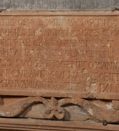 Zdjęcie nr 2: Epitafium złożone z dwóch tablic w kształcie leżącego prostokąta, dolnej z przedstawieniem zmarłego i górnej z inskrypcją. W dolnej tablicy, ujętej arabeską, ukazane nagie dziecko, leżące na marszczonej w równoległe fałdy tkaninie biegnącej pomiędzy jego udami. Nogi ma skrzyżowane. Prawa jest ułożona prosto, a lewa ugięta w kolanie. Jego głowa jest wsparta na zgiętej w łokciu lewej ręce, drugą rękę  ma ułożoną wzdłuż tułowia, w dłoni trzyma różę. Twarz jest pełna, nos krótki i szeroki, oczy zamknięte, usta pełne, lekko uśmiechnięte, na głowie krótkie, kręcone włosy. Pod lewą ręką znajduje się ludzka czaszka. Na tablicy powyżej inskrypcja "GENEROSOVS DOMINVS MARTINVS / CŻVRILO DE VIGNANO VICE VENA/TOR T[E]RRE CRACOVIENSIS ET / CAPITANEVS NIEPOL[O]MICENSIS / FILIO SVO PRIMOGENITO IOANNI / PONICNRAVIT QVI NATVS OBIIT / 26 IANVARII ANNO D(OMI)NI 1560  [V]IXIT HORIS TRIBVS".
