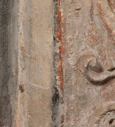 Zdjęcie nr 9: Epitafium złożone z dwóch tablic w kształcie leżącego prostokąta, dolnej z przedstawieniem zmarłego i górnej z inskrypcją. W dolnej tablicy, ujętej arabeską, ukazane nagie dziecko, leżące na marszczonej w równoległe fałdy tkaninie biegnącej pomiędzy jego udami. Nogi ma skrzyżowane. Prawa jest ułożona prosto, a lewa ugięta w kolanie. Jego głowa jest wsparta na zgiętej w łokciu lewej ręce, drugą rękę  ma ułożoną wzdłuż tułowia, w dłoni trzyma różę. Twarz jest pełna, nos krótki i szeroki, oczy zamknięte, usta pełne, lekko uśmiechnięte, na głowie krótkie, kręcone włosy. Pod lewą ręką znajduje się ludzka czaszka. Na tablicy powyżej inskrypcja "GENEROSOVS DOMINVS MARTINVS / CŻVRILO DE VIGNANO VICE VENA/TOR T[E]RRE CRACOVIENSIS ET / CAPITANEVS NIEPOL[O]MICENSIS / FILIO SVO PRIMOGENITO IOANNI / PONICNRAVIT QVI NATVS OBIIT / 26 IANVARII ANNO D(OMI)NI 1560  [V]IXIT HORIS TRIBVS".
