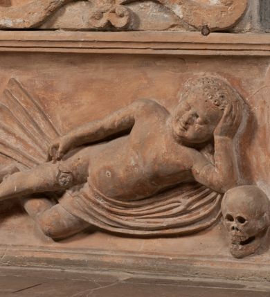 Zdjęcie nr 13: Epitafium złożone z dwóch tablic w kształcie leżącego prostokąta, dolnej z przedstawieniem zmarłego i górnej z inskrypcją. W dolnej tablicy, ujętej arabeską, ukazane nagie dziecko, leżące na marszczonej w równoległe fałdy tkaninie biegnącej pomiędzy jego udami. Nogi ma skrzyżowane. Prawa jest ułożona prosto, a lewa ugięta w kolanie. Jego głowa jest wsparta na zgiętej w łokciu lewej ręce, drugą rękę  ma ułożoną wzdłuż tułowia, w dłoni trzyma różę. Twarz jest pełna, nos krótki i szeroki, oczy zamknięte, usta pełne, lekko uśmiechnięte, na głowie krótkie, kręcone włosy. Pod lewą ręką znajduje się ludzka czaszka. Na tablicy powyżej inskrypcja "GENEROSOVS DOMINVS MARTINVS / CŻVRILO DE VIGNANO VICE VENA/TOR T[E]RRE CRACOVIENSIS ET / CAPITANEVS NIEPOL[O]MICENSIS / FILIO SVO PRIMOGENITO IOANNI / PONICNRAVIT QVI NATVS OBIIT / 26 IANVARII ANNO D(OMI)NI 1560  [V]IXIT HORIS TRIBVS".
