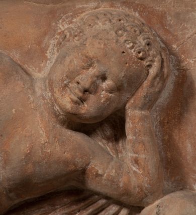 Zdjęcie nr 18: Epitafium złożone z dwóch tablic w kształcie leżącego prostokąta, dolnej z przedstawieniem zmarłego i górnej z inskrypcją. W dolnej tablicy, ujętej arabeską, ukazane nagie dziecko, leżące na marszczonej w równoległe fałdy tkaninie biegnącej pomiędzy jego udami. Nogi ma skrzyżowane. Prawa jest ułożona prosto, a lewa ugięta w kolanie. Jego głowa jest wsparta na zgiętej w łokciu lewej ręce, drugą rękę  ma ułożoną wzdłuż tułowia, w dłoni trzyma różę. Twarz jest pełna, nos krótki i szeroki, oczy zamknięte, usta pełne, lekko uśmiechnięte, na głowie krótkie, kręcone włosy. Pod lewą ręką znajduje się ludzka czaszka. Na tablicy powyżej inskrypcja "GENEROSOVS DOMINVS MARTINVS / CŻVRILO DE VIGNANO VICE VENA/TOR T[E]RRE CRACOVIENSIS ET / CAPITANEVS NIEPOL[O]MICENSIS / FILIO SVO PRIMOGENITO IOANNI / PONICNRAVIT QVI NATVS OBIIT / 26 IANVARII ANNO D(OMI)NI 1560  [V]IXIT HORIS TRIBVS".
