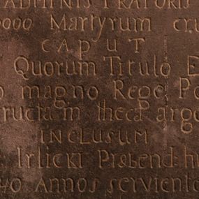 Zdjęcie nr 1: Tablica w kształcie stojącego prostokąta z inskrypcją: 
"D[eo]O[ptimo]M[aximo] / Ad perpetuam rei mamoriam et excitandium / cultum erga SS Martyres - / de consensu / Ill[ustrissi]mi R[evere]nd[issi]mi D[omini] Adalberti de Boza Wola / GORSKI/ Eppi[scopi] Kielc[ensi]: Diaecesis Tarnovien[sis]: Sede vacante / ADMINISTRATORIS / Ex n[ume]ro 10000 Martyrum crucifixorum / caput / unius sub Quorum Titulo Ecclesia haec / a Casimiro magno Rege Poloniarum / extructam theca argentea / inclusum / testelose Irlicki Praebend[atur] hic Ecclesiae / ultra 40 Annos serviente hic / Repositum / A[nno] D[omini] 1804 &amp; II 8bris"
