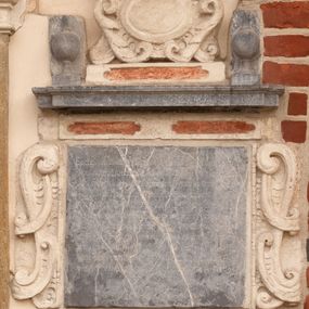 Zdjęcie nr 1: Tablica z wapienia dębnickiego w formie leżącego prostokąta. Flankowana uszakami z wapienia pińczowskiego utworzonymi z ornamentu małżowinowo-chrząstkowego. Wzdłuż górnej krawędzi płyty cokolik z wapienia pińczowskiego z dwiema płycinami polichromowanymi na czerwono. Ponad nim parapet z wapienia dębnickiego w formie gzymsu z dwoma wazonami, na nim mniejszy cokolik z wapienia pińczowskiego z płyciną polichromowaną na czerwono z kartuszem utworzonym z wolut i akantu, zwieńczony uskrzydloną główką anielską. W polu tablicy inskrypcja „D(EO) O(PTIMO) M(AXIMO) / ECCLE(SI)A HAEC EVDATA ET DOTATA PER SERENISS(IMO) CASIMIRVM AC / POLON(IAE) REGE(M) A(NNO) MCCCLIIII VETVSTATE AVTEM COLLAPSA REST/AVRATA PER ILL(USTRISSI)MOS RI PRINCIPES DVCES IN OSTROG ET / WISNIOWIEC COMITES IN WISNICZ IAROSŁAW ET TARNOW IOSEPH/VM CAROLVM ET THEOPHILAM LVBOMIRSCIOS MARE / SCHALCOS CVRIAE REGNI SANDOMIRIENSES NIEPOŁOM(ICENSES) ZA/TORIEN(SES) SOLECEN(SES) LUBACEN(SES) RICEN(SES) &amp; C(ETERA) CAPITANEOS ISTI/VS ECCL(ESI)AE BENEFACTORES NEC NON CVRAET SOLICITVDI/NE ADM(INISTARTORUM) R(EVERE)NDI(SSIMUS) THOMAE OLINSKI [C]VIVS PAROCHI AD FOR/MAM REDVCTATV QVI HAEC LECIS TANTIS BENEFACTO/RIBVS V TRAMQVE APPRECERE FELICITATEM A(NNO) D(OMINI) 1696”.