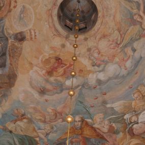 Zdjęcie nr 1: Iluzjonistyczną dekoracją malarską pokryto ściany kaplicy oraz strefę ponadcokołową: ściany tarczowe, pendentywy wokół stiukowych kartuszy herbowych oraz czaszę kopuły i wnętrze latarni. Ściany dolnej części podzielono na dwie strefy. Dolną tworzą zlokalizowane w narożach ścian iluzjonistycznie malowane pary nisz o konchach wypełnionych muszlą. W niszach ukazano osiem stojących frontalnie postaci starców, bez atrybutów i nimbów. Zapewne w ten sposób przedstawiono proroków lub apostołów. Każda z postaci ubrana jest w tunikę oraz płaszcz. Różnicuje je jedynie układ rąk, sposób kształtowania zarostu oraz kolorystyka szat. W drugiej strefie w przyłuczach arkad ukazano całopostaciowe przedstawienia uskrzydlonych aniołów trzymających narzędzia męki Pańskiej. Na ścianie wschodniej anioł prezentuje chustę Weroniki (z prawej) oraz latarnię (z lewej). Po bokach wejścia do kaplicy na ścianie północnej po prawej stronie anioł trzyma lancę i koronę cierniową, a po lewej krzyż. Z kolei na ścianie wschodniej po prawej ukazano anioła z drabiną, a po lewej z gąbką na trzcinie. Natomiast na ścianie południowej, po obu stronach zwieńczenia nagrobka, przedstawiono z prawej anioła z włócznią, a po lewej anioła z wiązką do biczowania. W tej strefie bezpośrednio przy łukach arkad wyobrażono leżące postacie geniuszy malowanych w technice en grisaille. Pod arkadą na ścianie wschodniej (ołtarzowej), ukazano dolną część owalnego jasno ugrowego baldachimu z lambrekinem i zielone, opadające paludamentum, rozsuwane kotarowo przez dwa uskrzydlone anioły. Dekoracja stanowi oprawę dla wiszącego tu obrazu Matki Boskiej z Dzieciątkiem w bogato rzeźbionej ramie. Z kolei na ścianie zachodniej wyobrażono monumentalną scenę Zdjęcia z krzyża. Jest to zwarta kompozycja ogniskująca się na wysokim drewnianym krzyżu, z którego ściągane jest martwe ciało Chrystusa. Z dwóch stron dłuższych ramion krzyż podtrzymują dwaj aniołowie. Ciało Jezusa opuszczane jest na białym pasie tkaniny przewiązanym pod jego ramionami. Chrystus ze zwisającą głową ma ręce ułożone wzdłuż ciała. Biodra przepasane ma białym perizonium. Jego skrzyżowane nogi są ugięte i jeszcze przybite gwoździem do krzyża. Gwóźdź wyciąga z nich obcęgami mężczyzna w niebieskiej, podwiniętej koszuli. Ciało opuszczają dwaj mężczyźni widoczni za poprzecznymi ramionami krzyża, trzymający końce taśmy. Człowiek z lewej strony w niebieskiej koszuli dodatkowo odbiera drugą białą taśmę od mężczyzny ubranego w szaroczarny strój. Osoba ta stoi na drabinie opartej o poprzeczne ramię krzyża. Drugi mężczyzna za krzyżem, w brązowej koszuli, lewą ręką trzyma koniec taśmy, a w uniesionej prawej młotek. Ciało Zbawiciela podtrzymuje lewą ręką kolejny mężczyzna stojący tyłem do widza na drugiej drabinie opartej o lewe ramię krzyża. Jest on ubrany w krótkie brązowe spodenki i bladozieloną koszulę. Pod krzyżem stoi zwarta siedmioosobowa grupa. Najprawdopodobniej z prawej strony ukazano św. Jana i Matkę Boską, na środku dwóch żołnierzy w ostro zakończonych hełmach, dwie kobiety, w tym zapewne Marię Magdalenę i starca widocznego z lewej strony kompozycji. Na ścianach tarczowych nad gzymsem wyobrażono po bokach okrągłych okien siedzących czterech ewangelistów i czterech ojców Kościoła. Na ścianie wschodniej znalazł się z prawej św. Jan z orłem, który w dziobie trzyma złoty kałamarz, a po lewej św. Mateusz rozmawiający z aniołem. Z kolei na ścianie południowej po lewej stronie przedstawiono św. Marka z lwem oraz św. Ambrożego trzymającego w prawej ręce naczynie z wylewającym się miodem. Na ścianie zachodniej z lewej znalazł się czytający św. Augustyn z sercem na dłoni, a z prawej św. Grzegorz Wielki z widoczną za nim tiarą i sową. Na ścianie północnej po lewej ukazano św. Hieronima z leżącym lwem, a po prawej stronie św. Łukasz z wołem. W pendentywach wykonano malarską dekorację w formie wijącej się wstęgi, na tle której widnieją stiukowe kartusze rollwerkowe, o owalnych kaboszonowych polach czwórdzielnych w krzyż. Po stronie wschodniej w pendentywach znajdują się dwa puste kartusze z niezachowanymi herbami. Natomiast herby zachowały się w pendentywach po stronie zachodniej. Na pendentywie północno-zachodnim: Jastrzębiec, Nowina, Gozdawa, Pobóg, a na południowo-zachodnim Gryf, Kotwicz, Kotwicz, Zabawa. W kopule wyobrażono Koronację Matki Boskiej adorowanej przez różnych świętych. Scenę koronacji Marii przez Trójcę Świętą przedstawiono w części wschodniej czaszy. Ukazana frontalnie Maria klęczy ze złożonymi rękami do modlitwy na obłokach. Ma owalną twarz okoloną jasnymi długimi włosami rozsypującymi się na jej ramiona. Na uniesionej ku górze głowie ma ubraną zsuwającą się białą chustę okrywającą włosy. Madonna ubrana jest w zasłaniający jej ramiona bladoniebieski płaszcz, opadający po bokach na obłoki. Nieznacznie wyżej z prawej strony na obłokach siedzi Bóg Ojciec. Wyobrażono go w trzech czwartych w prawo. Jest to starszy mężczyzna o siwych włosach i brodzie. W wyciągniętej prawej ręce nad głową Marii wraz z Chrystusem trzyma złotą koronę w typie zamkniętym. Z kolei w lewej podtrzymuje glob ze złotym krzyżykiem. Bóg Ojciec na głowie ma tiarę papieską. Ubrany jest w szaro-niebieską szatę oraz wzorzystą złotą kapę narzuconą na ramiona i spiętą pod szyją klamrą, z połami okrywającymi nogi. Naprzeciwko siedzi Chrystus widoczny w trzech czwartych w lewo z twarzą ukazaną w profilu. W wyciągniętej prawej ręce trzyma wraz z Bogiem Ojcem koronę, a lewą podtrzymuje złote berło. Chrystus ma jasne włosy opadające puklami na ramiona i podobną krótką brodę. Na głowie ma otwartą złotą koronę. Został przedstawiony z nagim torsem, na którym zaznaczono przebity bok. Jego postać otacza narzucony na ramiona bladoczerwony całun udrapowany w formie płaszcza. Nad koroną bliżej głowy Boga Ojca widoczna jest gołębica Ducha Świętego otoczona świetlistym otokiem. Ponad sceną koronacji wokół otworu do latarni wyobrażono wirujące złocisto-szare obłoki, na tle których widać uskrzydlone główki aniołków oraz postacie mniejszych i większych aniołków, które muzykują na różnych instrumentach, bądź też trzymają gałązki palmowe lub kwiaty albo kwiaty rozsypują. Uskrzydlone główki aniołków widoczne są także pośród obłoków, na których klęczy Madonna. Z prawej strony koronacji wyobrażono dwóch biskupów. Starszy, być może św. Wojciech, został przedstawiony w postawie półklęczącej w trzech czwartych w lewo. Prawą ręką zdaje się wskazywać na scenę koronacji, lewą zaś przyciska do piersi. Ma odkrytą głowę z widocznymi siwymi włosami i taką samą brodą. Ubrany jest w niebiesko-zielonkawą kapę ze złotym kapturem zakończonym chwostem. Na ziemi przy jego stopie widoczna jest złota infuła. Świętemu przyglądają się dwaj aniołowie widoczni z tyłu. Za nim klęczy młodszy biskup z leżącym przy nim na ziemi pastorałem i mieczem. Zapewne jest to św. Stanisław ze Szczepanowa. Święty ukazany został frontalnie z prawą ręką przyciśniętą do piersi, a z lewą nieznacznie odsuniętą w bok. Ma pociągłą twarz o krótkich jasnych włosach i podobnym zaroście. Ubrany jest w albę oraz szaro-bordową kapę o złotym kapturze. Przy jego kolanach stoi złota infuła, a za nim widoczny jest anioł z gałązką palmową. Za św. Stanisławem w rozwianych szatach klęczy św. Jadwiga Śląska, którą identyfikuje bryła kościoła widoczna przy jej stopach. Postać Jadwigi ukazano w profilu z założonymi rękami przed sobą. Na głowie ma niewielką złotą koronę, spod której widoczna jest biała chusta okrywająca włosy. Ubrana jest w bladoczerwoną suknię przepasaną w talii i narzucony na ramiona bladoszkarłatny płaszcz z gronostajowym kołnierzem i obszyciem. Za św. Jadwigą stoi inna święta z odsłoniętą lewą ręką wspartą o bok. Brak atrybutu nie pozwala na jej identyfikację. Ukazano ją w trzech czwartych w prawo z głową w profilu. Ma owalną twarz z wydatnym nosem. Na głowie ma niewielką złotą koronę, spod której widać jasną chustę okrywającą włosy. Ubrana jest w złocisto-szarą suknię z krótkimi rękawami i bladoczerwony rozwiany płaszcz. Pomiędzy obiema kobietami widać dwie postacie uskrzydlonych aniołów. Za świętymi siedzi z otwartą księgą wyobrażony frontalnie św. Jana Kanty. Jest to mężczyzna w średnim wieku z wysokim czołem, krótkimi brązowymi włosami i podobną brodą. Ubrany jest w bladofioletową togę akademicką z gronostajową peleryną. Trzymana przez niego księga ma czerwone okładki. Obok św. Jana Kantego namalowano czteroosobową grupę starszych mężczyzn. Pierwszy z nich, ujętych w trzech czwartych w prawo, zdaje się przyklękając, odbierać prawą ręką palmę męczeństwa podawaną mu przez widocznego nad nim anioła. Lewą ma ułożoną wzdłuż ciała. Ma podłużną twarz widoczną z profilu, otoczoną białymi włosami i spiczastą białą brodą. Ubrany jest w rozwianą jasnobeżową szatę przewiązaną w pasie i taki sam płaszcz narzucony na prawe ramię. Lewy rękaw tuniki jest podciągnięty, odsłaniając przedramię ręki. Na lewej nodze widoczny jest sandał. Za nim przedstawiono klęczącego w ujęciu trzech czwartych w lewo zakonnika eremitę, być może św. Pawła Pustelnika w białym habicie paulińskim. Zakonnik na wysokości bioder ma rozsunięte ręce. Jego twarz o wydatnym nosie otacza krzaczasta, długa, biała broda oraz białe włosy. W głębi za nim częściowo widać dwóch innych brodatych mężczyzn w beżowych szatach. Jeden z nich trzyma w dłoni palmę. W niewielkiej odległości za grupą mężczyzn na pierwszym planie klęczy na obłoku ukazany frontalnie św. Jacek. W rękach uniesionych na wysokości piersi trzyma wieżycową, złotą monstrancję i figurę Matki Boskiej. Dominikanin został przedstawiony z wysokim łysym czołem i wianuszkiem siwiejących włosów. Jego pociągła twarz o wyrazistym nosie i wąskich, nieznacznie zaciśniętych ustach pozbawiona jest zarostu. Ubrany jest w dominikański habit z czarnoniebieskim płaszczem. Z lewej strony sceny koronacji namalowano grupę czterech świętych. Na pierwszym planie widać klęczącego św. Stanisława Kostkę, wspartego na długim kiju z przywiązanym do niego węzełkiem. Święty został przedstawiony w profilu. Ma młodzieńczą, owalną twarz z krótkimi brązowymi włosami i rumianymi policzkami. Ubrany jest w bladobeżowy płaszcz, spod którego widać jasnoseledynową szatę. Za Stanisławem Kostką wyłania się w półpostaci św. Jan Nepomucen z drewnianym krzyżem podtrzymywanym lewą ręką. Jest to dojrzały mężczyzna o pociągłej twarzy, z brązowymi włosami i brodą. Z prawej strony św. Stanisława Kostki ukazano stojące dwie zakonnice, św. Kingę i zapewne bł. Salomeę. Kingę ukazano frontalnie w kontrapoście z głową uniesioną ku niebu w jasnobeżowym habicie klaryski wpadającym w brąz. Księżna prawą ręką przyciska do piersi bryłę soli, a w opuszczonej lewej trzyma kwiat lilii. U jej stóp widać model kościoła klasztornego w Starym Sączu. Obok stoi najprawdopodobniej bł. Salomea. Ukazano ją w mocnym kontrapoście, z dłońmi splecionymi na piersi i spojrzeniem skierowanym ku ziemi. Ubrana jest w rozwiany szaroniebieski habit i jasny welon. Wnętrze latarni wypełniają uskrzydlone głowy aniołków na tle złocisto-szarych obłoków.    







