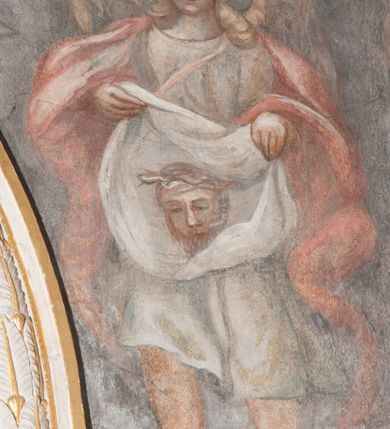 Zdjęcie nr 29: Iluzjonistyczną dekoracją malarską pokryto ściany kaplicy oraz strefę ponadcokołową: ściany tarczowe, pendentywy wokół stiukowych kartuszy herbowych oraz czaszę kopuły i wnętrze latarni. Ściany dolnej części podzielono na dwie strefy. Dolną tworzą zlokalizowane w narożach ścian iluzjonistycznie malowane pary nisz o konchach wypełnionych muszlą. W niszach ukazano osiem stojących frontalnie postaci starców, bez atrybutów i nimbów. Zapewne w ten sposób przedstawiono proroków lub apostołów. Każda z postaci ubrana jest w tunikę oraz płaszcz. Różnicuje je jedynie układ rąk, sposób kształtowania zarostu oraz kolorystyka szat. W drugiej strefie w przyłuczach arkad ukazano całopostaciowe przedstawienia uskrzydlonych aniołów trzymających narzędzia męki Pańskiej. Na ścianie wschodniej anioł prezentuje chustę Weroniki (z prawej) oraz latarnię (z lewej). Po bokach wejścia do kaplicy na ścianie północnej po prawej stronie anioł trzyma lancę i koronę cierniową, a po lewej krzyż. Z kolei na ścianie wschodniej po prawej ukazano anioła z drabiną, a po lewej z gąbką na trzcinie. Natomiast na ścianie południowej, po obu stronach zwieńczenia nagrobka, przedstawiono z prawej anioła z włócznią, a po lewej anioła z wiązką do biczowania. W tej strefie bezpośrednio przy łukach arkad wyobrażono leżące postacie geniuszy malowanych w technice en grisaille. Pod arkadą na ścianie wschodniej (ołtarzowej), ukazano dolną część owalnego jasno ugrowego baldachimu z lambrekinem i zielone, opadające paludamentum, rozsuwane kotarowo przez dwa uskrzydlone anioły. Dekoracja stanowi oprawę dla wiszącego tu obrazu Matki Boskiej z Dzieciątkiem w bogato rzeźbionej ramie. Z kolei na ścianie zachodniej wyobrażono monumentalną scenę Zdjęcia z krzyża. Jest to zwarta kompozycja ogniskująca się na wysokim drewnianym krzyżu, z którego ściągane jest martwe ciało Chrystusa. Z dwóch stron dłuższych ramion krzyż podtrzymują dwaj aniołowie. Ciało Jezusa opuszczane jest na białym pasie tkaniny przewiązanym pod jego ramionami. Chrystus ze zwisającą głową ma ręce ułożone wzdłuż ciała. Biodra przepasane ma białym perizonium. Jego skrzyżowane nogi są ugięte i jeszcze przybite gwoździem do krzyża. Gwóźdź wyciąga z nich obcęgami mężczyzna w niebieskiej, podwiniętej koszuli. Ciało opuszczają dwaj mężczyźni widoczni za poprzecznymi ramionami krzyża, trzymający końce taśmy. Człowiek z lewej strony w niebieskiej koszuli dodatkowo odbiera drugą białą taśmę od mężczyzny ubranego w szaroczarny strój. Osoba ta stoi na drabinie opartej o poprzeczne ramię krzyża. Drugi mężczyzna za krzyżem, w brązowej koszuli, lewą ręką trzyma koniec taśmy, a w uniesionej prawej młotek. Ciało Zbawiciela podtrzymuje lewą ręką kolejny mężczyzna stojący tyłem do widza na drugiej drabinie opartej o lewe ramię krzyża. Jest on ubrany w krótkie brązowe spodenki i bladozieloną koszulę. Pod krzyżem stoi zwarta siedmioosobowa grupa. Najprawdopodobniej z prawej strony ukazano św. Jana i Matkę Boską, na środku dwóch żołnierzy w ostro zakończonych hełmach, dwie kobiety, w tym zapewne Marię Magdalenę i starca widocznego z lewej strony kompozycji. Na ścianach tarczowych nad gzymsem wyobrażono po bokach okrągłych okien siedzących czterech ewangelistów i czterech ojców Kościoła. Na ścianie wschodniej znalazł się z prawej św. Jan z orłem, który w dziobie trzyma złoty kałamarz, a po lewej św. Mateusz rozmawiający z aniołem. Z kolei na ścianie południowej po lewej stronie przedstawiono św. Marka z lwem oraz św. Ambrożego trzymającego w prawej ręce naczynie z wylewającym się miodem. Na ścianie zachodniej z lewej znalazł się czytający św. Augustyn z sercem na dłoni, a z prawej św. Grzegorz Wielki z widoczną za nim tiarą i sową. Na ścianie północnej po lewej ukazano św. Hieronima z leżącym lwem, a po prawej stronie św. Łukasz z wołem. W pendentywach wykonano malarską dekorację w formie wijącej się wstęgi, na tle której widnieją stiukowe kartusze rollwerkowe, o owalnych kaboszonowych polach czwórdzielnych w krzyż. Po stronie wschodniej w pendentywach znajdują się dwa puste kartusze z niezachowanymi herbami. Natomiast herby zachowały się w pendentywach po stronie zachodniej. Na pendentywie północno-zachodnim: Jastrzębiec, Nowina, Gozdawa, Pobóg, a na południowo-zachodnim Gryf, Kotwicz, Kotwicz, Zabawa. W kopule wyobrażono Koronację Matki Boskiej adorowanej przez różnych świętych. Scenę koronacji Marii przez Trójcę Świętą przedstawiono w części wschodniej czaszy. Ukazana frontalnie Maria klęczy ze złożonymi rękami do modlitwy na obłokach. Ma owalną twarz okoloną jasnymi długimi włosami rozsypującymi się na jej ramiona. Na uniesionej ku górze głowie ma ubraną zsuwającą się białą chustę okrywającą włosy. Madonna ubrana jest w zasłaniający jej ramiona bladoniebieski płaszcz, opadający po bokach na obłoki. Nieznacznie wyżej z prawej strony na obłokach siedzi Bóg Ojciec. Wyobrażono go w trzech czwartych w prawo. Jest to starszy mężczyzna o siwych włosach i brodzie. W wyciągniętej prawej ręce nad głową Marii wraz z Chrystusem trzyma złotą koronę w typie zamkniętym. Z kolei w lewej podtrzymuje glob ze złotym krzyżykiem. Bóg Ojciec na głowie ma tiarę papieską. Ubrany jest w szaro-niebieską szatę oraz wzorzystą złotą kapę narzuconą na ramiona i spiętą pod szyją klamrą, z połami okrywającymi nogi. Naprzeciwko siedzi Chrystus widoczny w trzech czwartych w lewo z twarzą ukazaną w profilu. W wyciągniętej prawej ręce trzyma wraz z Bogiem Ojcem koronę, a lewą podtrzymuje złote berło. Chrystus ma jasne włosy opadające puklami na ramiona i podobną krótką brodę. Na głowie ma otwartą złotą koronę. Został przedstawiony z nagim torsem, na którym zaznaczono przebity bok. Jego postać otacza narzucony na ramiona bladoczerwony całun udrapowany w formie płaszcza. Nad koroną bliżej głowy Boga Ojca widoczna jest gołębica Ducha Świętego otoczona świetlistym otokiem. Ponad sceną koronacji wokół otworu do latarni wyobrażono wirujące złocisto-szare obłoki, na tle których widać uskrzydlone główki aniołków oraz postacie mniejszych i większych aniołków, które muzykują na różnych instrumentach, bądź też trzymają gałązki palmowe lub kwiaty albo kwiaty rozsypują. Uskrzydlone główki aniołków widoczne są także pośród obłoków, na których klęczy Madonna. Z prawej strony koronacji wyobrażono dwóch biskupów. Starszy, być może św. Wojciech, został przedstawiony w postawie półklęczącej w trzech czwartych w lewo. Prawą ręką zdaje się wskazywać na scenę koronacji, lewą zaś przyciska do piersi. Ma odkrytą głowę z widocznymi siwymi włosami i taką samą brodą. Ubrany jest w niebiesko-zielonkawą kapę ze złotym kapturem zakończonym chwostem. Na ziemi przy jego stopie widoczna jest złota infuła. Świętemu przyglądają się dwaj aniołowie widoczni z tyłu. Za nim klęczy młodszy biskup z leżącym przy nim na ziemi pastorałem i mieczem. Zapewne jest to św. Stanisław ze Szczepanowa. Święty ukazany został frontalnie z prawą ręką przyciśniętą do piersi, a z lewą nieznacznie odsuniętą w bok. Ma pociągłą twarz o krótkich jasnych włosach i podobnym zaroście. Ubrany jest w albę oraz szaro-bordową kapę o złotym kapturze. Przy jego kolanach stoi złota infuła, a za nim widoczny jest anioł z gałązką palmową. Za św. Stanisławem w rozwianych szatach klęczy św. Jadwiga Śląska, którą identyfikuje bryła kościoła widoczna przy jej stopach. Postać Jadwigi ukazano w profilu z założonymi rękami przed sobą. Na głowie ma niewielką złotą koronę, spod której widoczna jest biała chusta okrywająca włosy. Ubrana jest w bladoczerwoną suknię przepasaną w talii i narzucony na ramiona bladoszkarłatny płaszcz z gronostajowym kołnierzem i obszyciem. Za św. Jadwigą stoi inna święta z odsłoniętą lewą ręką wspartą o bok. Brak atrybutu nie pozwala na jej identyfikację. Ukazano ją w trzech czwartych w prawo z głową w profilu. Ma owalną twarz z wydatnym nosem. Na głowie ma niewielką złotą koronę, spod której widać jasną chustę okrywającą włosy. Ubrana jest w złocisto-szarą suknię z krótkimi rękawami i bladoczerwony rozwiany płaszcz. Pomiędzy obiema kobietami widać dwie postacie uskrzydlonych aniołów. Za świętymi siedzi z otwartą księgą wyobrażony frontalnie św. Jana Kanty. Jest to mężczyzna w średnim wieku z wysokim czołem, krótkimi brązowymi włosami i podobną brodą. Ubrany jest w bladofioletową togę akademicką z gronostajową peleryną. Trzymana przez niego księga ma czerwone okładki. Obok św. Jana Kantego namalowano czteroosobową grupę starszych mężczyzn. Pierwszy z nich, ujętych w trzech czwartych w prawo, zdaje się przyklękając, odbierać prawą ręką palmę męczeństwa podawaną mu przez widocznego nad nim anioła. Lewą ma ułożoną wzdłuż ciała. Ma podłużną twarz widoczną z profilu, otoczoną białymi włosami i spiczastą białą brodą. Ubrany jest w rozwianą jasnobeżową szatę przewiązaną w pasie i taki sam płaszcz narzucony na prawe ramię. Lewy rękaw tuniki jest podciągnięty, odsłaniając przedramię ręki. Na lewej nodze widoczny jest sandał. Za nim przedstawiono klęczącego w ujęciu trzech czwartych w lewo zakonnika eremitę, być może św. Pawła Pustelnika w białym habicie paulińskim. Zakonnik na wysokości bioder ma rozsunięte ręce. Jego twarz o wydatnym nosie otacza krzaczasta, długa, biała broda oraz białe włosy. W głębi za nim częściowo widać dwóch innych brodatych mężczyzn w beżowych szatach. Jeden z nich trzyma w dłoni palmę. W niewielkiej odległości za grupą mężczyzn na pierwszym planie klęczy na obłoku ukazany frontalnie św. Jacek. W rękach uniesionych na wysokości piersi trzyma wieżycową, złotą monstrancję i figurę Matki Boskiej. Dominikanin został przedstawiony z wysokim łysym czołem i wianuszkiem siwiejących włosów. Jego pociągła twarz o wyrazistym nosie i wąskich, nieznacznie zaciśniętych ustach pozbawiona jest zarostu. Ubrany jest w dominikański habit z czarnoniebieskim płaszczem. Z lewej strony sceny koronacji namalowano grupę czterech świętych. Na pierwszym planie widać klęczącego św. Stanisława Kostkę, wspartego na długim kiju z przywiązanym do niego węzełkiem. Święty został przedstawiony w profilu. Ma młodzieńczą, owalną twarz z krótkimi brązowymi włosami i rumianymi policzkami. Ubrany jest w bladobeżowy płaszcz, spod którego widać jasnoseledynową szatę. Za Stanisławem Kostką wyłania się w półpostaci św. Jan Nepomucen z drewnianym krzyżem podtrzymywanym lewą ręką. Jest to dojrzały mężczyzna o pociągłej twarzy, z brązowymi włosami i brodą. Z prawej strony św. Stanisława Kostki ukazano stojące dwie zakonnice, św. Kingę i zapewne bł. Salomeę. Kingę ukazano frontalnie w kontrapoście z głową uniesioną ku niebu w jasnobeżowym habicie klaryski wpadającym w brąz. Księżna prawą ręką przyciska do piersi bryłę soli, a w opuszczonej lewej trzyma kwiat lilii. U jej stóp widać model kościoła klasztornego w Starym Sączu. Obok stoi najprawdopodobniej bł. Salomea. Ukazano ją w mocnym kontrapoście, z dłońmi splecionymi na piersi i spojrzeniem skierowanym ku ziemi. Ubrana jest w rozwiany szaroniebieski habit i jasny welon. Wnętrze latarni wypełniają uskrzydlone głowy aniołków na tle złocisto-szarych obłoków.    







