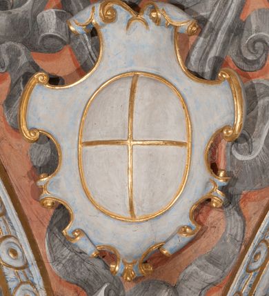 Zdjęcie nr 50: Iluzjonistyczną dekoracją malarską pokryto ściany kaplicy oraz strefę ponadcokołową: ściany tarczowe, pendentywy wokół stiukowych kartuszy herbowych oraz czaszę kopuły i wnętrze latarni. Ściany dolnej części podzielono na dwie strefy. Dolną tworzą zlokalizowane w narożach ścian iluzjonistycznie malowane pary nisz o konchach wypełnionych muszlą. W niszach ukazano osiem stojących frontalnie postaci starców, bez atrybutów i nimbów. Zapewne w ten sposób przedstawiono proroków lub apostołów. Każda z postaci ubrana jest w tunikę oraz płaszcz. Różnicuje je jedynie układ rąk, sposób kształtowania zarostu oraz kolorystyka szat. W drugiej strefie w przyłuczach arkad ukazano całopostaciowe przedstawienia uskrzydlonych aniołów trzymających narzędzia męki Pańskiej. Na ścianie wschodniej anioł prezentuje chustę Weroniki (z prawej) oraz latarnię (z lewej). Po bokach wejścia do kaplicy na ścianie północnej po prawej stronie anioł trzyma lancę i koronę cierniową, a po lewej krzyż. Z kolei na ścianie wschodniej po prawej ukazano anioła z drabiną, a po lewej z gąbką na trzcinie. Natomiast na ścianie południowej, po obu stronach zwieńczenia nagrobka, przedstawiono z prawej anioła z włócznią, a po lewej anioła z wiązką do biczowania. W tej strefie bezpośrednio przy łukach arkad wyobrażono leżące postacie geniuszy malowanych w technice en grisaille. Pod arkadą na ścianie wschodniej (ołtarzowej), ukazano dolną część owalnego jasno ugrowego baldachimu z lambrekinem i zielone, opadające paludamentum, rozsuwane kotarowo przez dwa uskrzydlone anioły. Dekoracja stanowi oprawę dla wiszącego tu obrazu Matki Boskiej z Dzieciątkiem w bogato rzeźbionej ramie. Z kolei na ścianie zachodniej wyobrażono monumentalną scenę Zdjęcia z krzyża. Jest to zwarta kompozycja ogniskująca się na wysokim drewnianym krzyżu, z którego ściągane jest martwe ciało Chrystusa. Z dwóch stron dłuższych ramion krzyż podtrzymują dwaj aniołowie. Ciało Jezusa opuszczane jest na białym pasie tkaniny przewiązanym pod jego ramionami. Chrystus ze zwisającą głową ma ręce ułożone wzdłuż ciała. Biodra przepasane ma białym perizonium. Jego skrzyżowane nogi są ugięte i jeszcze przybite gwoździem do krzyża. Gwóźdź wyciąga z nich obcęgami mężczyzna w niebieskiej, podwiniętej koszuli. Ciało opuszczają dwaj mężczyźni widoczni za poprzecznymi ramionami krzyża, trzymający końce taśmy. Człowiek z lewej strony w niebieskiej koszuli dodatkowo odbiera drugą białą taśmę od mężczyzny ubranego w szaroczarny strój. Osoba ta stoi na drabinie opartej o poprzeczne ramię krzyża. Drugi mężczyzna za krzyżem, w brązowej koszuli, lewą ręką trzyma koniec taśmy, a w uniesionej prawej młotek. Ciało Zbawiciela podtrzymuje lewą ręką kolejny mężczyzna stojący tyłem do widza na drugiej drabinie opartej o lewe ramię krzyża. Jest on ubrany w krótkie brązowe spodenki i bladozieloną koszulę. Pod krzyżem stoi zwarta siedmioosobowa grupa. Najprawdopodobniej z prawej strony ukazano św. Jana i Matkę Boską, na środku dwóch żołnierzy w ostro zakończonych hełmach, dwie kobiety, w tym zapewne Marię Magdalenę i starca widocznego z lewej strony kompozycji. Na ścianach tarczowych nad gzymsem wyobrażono po bokach okrągłych okien siedzących czterech ewangelistów i czterech ojców Kościoła. Na ścianie wschodniej znalazł się z prawej św. Jan z orłem, który w dziobie trzyma złoty kałamarz, a po lewej św. Mateusz rozmawiający z aniołem. Z kolei na ścianie południowej po lewej stronie przedstawiono św. Marka z lwem oraz św. Ambrożego trzymającego w prawej ręce naczynie z wylewającym się miodem. Na ścianie zachodniej z lewej znalazł się czytający św. Augustyn z sercem na dłoni, a z prawej św. Grzegorz Wielki z widoczną za nim tiarą i sową. Na ścianie północnej po lewej ukazano św. Hieronima z leżącym lwem, a po prawej stronie św. Łukasz z wołem. W pendentywach wykonano malarską dekorację w formie wijącej się wstęgi, na tle której widnieją stiukowe kartusze rollwerkowe, o owalnych kaboszonowych polach czwórdzielnych w krzyż. Po stronie wschodniej w pendentywach znajdują się dwa puste kartusze z niezachowanymi herbami. Natomiast herby zachowały się w pendentywach po stronie zachodniej. Na pendentywie północno-zachodnim: Jastrzębiec, Nowina, Gozdawa, Pobóg, a na południowo-zachodnim Gryf, Kotwicz, Kotwicz, Zabawa. W kopule wyobrażono Koronację Matki Boskiej adorowanej przez różnych świętych. Scenę koronacji Marii przez Trójcę Świętą przedstawiono w części wschodniej czaszy. Ukazana frontalnie Maria klęczy ze złożonymi rękami do modlitwy na obłokach. Ma owalną twarz okoloną jasnymi długimi włosami rozsypującymi się na jej ramiona. Na uniesionej ku górze głowie ma ubraną zsuwającą się białą chustę okrywającą włosy. Madonna ubrana jest w zasłaniający jej ramiona bladoniebieski płaszcz, opadający po bokach na obłoki. Nieznacznie wyżej z prawej strony na obłokach siedzi Bóg Ojciec. Wyobrażono go w trzech czwartych w prawo. Jest to starszy mężczyzna o siwych włosach i brodzie. W wyciągniętej prawej ręce nad głową Marii wraz z Chrystusem trzyma złotą koronę w typie zamkniętym. Z kolei w lewej podtrzymuje glob ze złotym krzyżykiem. Bóg Ojciec na głowie ma tiarę papieską. Ubrany jest w szaro-niebieską szatę oraz wzorzystą złotą kapę narzuconą na ramiona i spiętą pod szyją klamrą, z połami okrywającymi nogi. Naprzeciwko siedzi Chrystus widoczny w trzech czwartych w lewo z twarzą ukazaną w profilu. W wyciągniętej prawej ręce trzyma wraz z Bogiem Ojcem koronę, a lewą podtrzymuje złote berło. Chrystus ma jasne włosy opadające puklami na ramiona i podobną krótką brodę. Na głowie ma otwartą złotą koronę. Został przedstawiony z nagim torsem, na którym zaznaczono przebity bok. Jego postać otacza narzucony na ramiona bladoczerwony całun udrapowany w formie płaszcza. Nad koroną bliżej głowy Boga Ojca widoczna jest gołębica Ducha Świętego otoczona świetlistym otokiem. Ponad sceną koronacji wokół otworu do latarni wyobrażono wirujące złocisto-szare obłoki, na tle których widać uskrzydlone główki aniołków oraz postacie mniejszych i większych aniołków, które muzykują na różnych instrumentach, bądź też trzymają gałązki palmowe lub kwiaty albo kwiaty rozsypują. Uskrzydlone główki aniołków widoczne są także pośród obłoków, na których klęczy Madonna. Z prawej strony koronacji wyobrażono dwóch biskupów. Starszy, być może św. Wojciech, został przedstawiony w postawie półklęczącej w trzech czwartych w lewo. Prawą ręką zdaje się wskazywać na scenę koronacji, lewą zaś przyciska do piersi. Ma odkrytą głowę z widocznymi siwymi włosami i taką samą brodą. Ubrany jest w niebiesko-zielonkawą kapę ze złotym kapturem zakończonym chwostem. Na ziemi przy jego stopie widoczna jest złota infuła. Świętemu przyglądają się dwaj aniołowie widoczni z tyłu. Za nim klęczy młodszy biskup z leżącym przy nim na ziemi pastorałem i mieczem. Zapewne jest to św. Stanisław ze Szczepanowa. Święty ukazany został frontalnie z prawą ręką przyciśniętą do piersi, a z lewą nieznacznie odsuniętą w bok. Ma pociągłą twarz o krótkich jasnych włosach i podobnym zaroście. Ubrany jest w albę oraz szaro-bordową kapę o złotym kapturze. Przy jego kolanach stoi złota infuła, a za nim widoczny jest anioł z gałązką palmową. Za św. Stanisławem w rozwianych szatach klęczy św. Jadwiga Śląska, którą identyfikuje bryła kościoła widoczna przy jej stopach. Postać Jadwigi ukazano w profilu z założonymi rękami przed sobą. Na głowie ma niewielką złotą koronę, spod której widoczna jest biała chusta okrywająca włosy. Ubrana jest w bladoczerwoną suknię przepasaną w talii i narzucony na ramiona bladoszkarłatny płaszcz z gronostajowym kołnierzem i obszyciem. Za św. Jadwigą stoi inna święta z odsłoniętą lewą ręką wspartą o bok. Brak atrybutu nie pozwala na jej identyfikację. Ukazano ją w trzech czwartych w prawo z głową w profilu. Ma owalną twarz z wydatnym nosem. Na głowie ma niewielką złotą koronę, spod której widać jasną chustę okrywającą włosy. Ubrana jest w złocisto-szarą suknię z krótkimi rękawami i bladoczerwony rozwiany płaszcz. Pomiędzy obiema kobietami widać dwie postacie uskrzydlonych aniołów. Za świętymi siedzi z otwartą księgą wyobrażony frontalnie św. Jana Kanty. Jest to mężczyzna w średnim wieku z wysokim czołem, krótkimi brązowymi włosami i podobną brodą. Ubrany jest w bladofioletową togę akademicką z gronostajową peleryną. Trzymana przez niego księga ma czerwone okładki. Obok św. Jana Kantego namalowano czteroosobową grupę starszych mężczyzn. Pierwszy z nich, ujętych w trzech czwartych w prawo, zdaje się przyklękając, odbierać prawą ręką palmę męczeństwa podawaną mu przez widocznego nad nim anioła. Lewą ma ułożoną wzdłuż ciała. Ma podłużną twarz widoczną z profilu, otoczoną białymi włosami i spiczastą białą brodą. Ubrany jest w rozwianą jasnobeżową szatę przewiązaną w pasie i taki sam płaszcz narzucony na prawe ramię. Lewy rękaw tuniki jest podciągnięty, odsłaniając przedramię ręki. Na lewej nodze widoczny jest sandał. Za nim przedstawiono klęczącego w ujęciu trzech czwartych w lewo zakonnika eremitę, być może św. Pawła Pustelnika w białym habicie paulińskim. Zakonnik na wysokości bioder ma rozsunięte ręce. Jego twarz o wydatnym nosie otacza krzaczasta, długa, biała broda oraz białe włosy. W głębi za nim częściowo widać dwóch innych brodatych mężczyzn w beżowych szatach. Jeden z nich trzyma w dłoni palmę. W niewielkiej odległości za grupą mężczyzn na pierwszym planie klęczy na obłoku ukazany frontalnie św. Jacek. W rękach uniesionych na wysokości piersi trzyma wieżycową, złotą monstrancję i figurę Matki Boskiej. Dominikanin został przedstawiony z wysokim łysym czołem i wianuszkiem siwiejących włosów. Jego pociągła twarz o wyrazistym nosie i wąskich, nieznacznie zaciśniętych ustach pozbawiona jest zarostu. Ubrany jest w dominikański habit z czarnoniebieskim płaszczem. Z lewej strony sceny koronacji namalowano grupę czterech świętych. Na pierwszym planie widać klęczącego św. Stanisława Kostkę, wspartego na długim kiju z przywiązanym do niego węzełkiem. Święty został przedstawiony w profilu. Ma młodzieńczą, owalną twarz z krótkimi brązowymi włosami i rumianymi policzkami. Ubrany jest w bladobeżowy płaszcz, spod którego widać jasnoseledynową szatę. Za Stanisławem Kostką wyłania się w półpostaci św. Jan Nepomucen z drewnianym krzyżem podtrzymywanym lewą ręką. Jest to dojrzały mężczyzna o pociągłej twarzy, z brązowymi włosami i brodą. Z prawej strony św. Stanisława Kostki ukazano stojące dwie zakonnice, św. Kingę i zapewne bł. Salomeę. Kingę ukazano frontalnie w kontrapoście z głową uniesioną ku niebu w jasnobeżowym habicie klaryski wpadającym w brąz. Księżna prawą ręką przyciska do piersi bryłę soli, a w opuszczonej lewej trzyma kwiat lilii. U jej stóp widać model kościoła klasztornego w Starym Sączu. Obok stoi najprawdopodobniej bł. Salomea. Ukazano ją w mocnym kontrapoście, z dłońmi splecionymi na piersi i spojrzeniem skierowanym ku ziemi. Ubrana jest w rozwiany szaroniebieski habit i jasny welon. Wnętrze latarni wypełniają uskrzydlone głowy aniołków na tle złocisto-szarych obłoków.    







