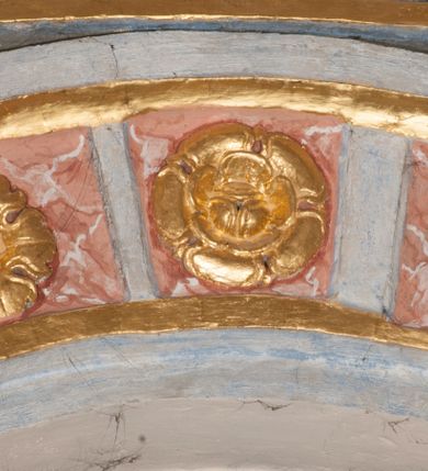 Zdjęcie nr 51: Iluzjonistyczną dekoracją malarską pokryto ściany kaplicy oraz strefę ponadcokołową: ściany tarczowe, pendentywy wokół stiukowych kartuszy herbowych oraz czaszę kopuły i wnętrze latarni. Ściany dolnej części podzielono na dwie strefy. Dolną tworzą zlokalizowane w narożach ścian iluzjonistycznie malowane pary nisz o konchach wypełnionych muszlą. W niszach ukazano osiem stojących frontalnie postaci starców, bez atrybutów i nimbów. Zapewne w ten sposób przedstawiono proroków lub apostołów. Każda z postaci ubrana jest w tunikę oraz płaszcz. Różnicuje je jedynie układ rąk, sposób kształtowania zarostu oraz kolorystyka szat. W drugiej strefie w przyłuczach arkad ukazano całopostaciowe przedstawienia uskrzydlonych aniołów trzymających narzędzia męki Pańskiej. Na ścianie wschodniej anioł prezentuje chustę Weroniki (z prawej) oraz latarnię (z lewej). Po bokach wejścia do kaplicy na ścianie północnej po prawej stronie anioł trzyma lancę i koronę cierniową, a po lewej krzyż. Z kolei na ścianie wschodniej po prawej ukazano anioła z drabiną, a po lewej z gąbką na trzcinie. Natomiast na ścianie południowej, po obu stronach zwieńczenia nagrobka, przedstawiono z prawej anioła z włócznią, a po lewej anioła z wiązką do biczowania. W tej strefie bezpośrednio przy łukach arkad wyobrażono leżące postacie geniuszy malowanych w technice en grisaille. Pod arkadą na ścianie wschodniej (ołtarzowej), ukazano dolną część owalnego jasno ugrowego baldachimu z lambrekinem i zielone, opadające paludamentum, rozsuwane kotarowo przez dwa uskrzydlone anioły. Dekoracja stanowi oprawę dla wiszącego tu obrazu Matki Boskiej z Dzieciątkiem w bogato rzeźbionej ramie. Z kolei na ścianie zachodniej wyobrażono monumentalną scenę Zdjęcia z krzyża. Jest to zwarta kompozycja ogniskująca się na wysokim drewnianym krzyżu, z którego ściągane jest martwe ciało Chrystusa. Z dwóch stron dłuższych ramion krzyż podtrzymują dwaj aniołowie. Ciało Jezusa opuszczane jest na białym pasie tkaniny przewiązanym pod jego ramionami. Chrystus ze zwisającą głową ma ręce ułożone wzdłuż ciała. Biodra przepasane ma białym perizonium. Jego skrzyżowane nogi są ugięte i jeszcze przybite gwoździem do krzyża. Gwóźdź wyciąga z nich obcęgami mężczyzna w niebieskiej, podwiniętej koszuli. Ciało opuszczają dwaj mężczyźni widoczni za poprzecznymi ramionami krzyża, trzymający końce taśmy. Człowiek z lewej strony w niebieskiej koszuli dodatkowo odbiera drugą białą taśmę od mężczyzny ubranego w szaroczarny strój. Osoba ta stoi na drabinie opartej o poprzeczne ramię krzyża. Drugi mężczyzna za krzyżem, w brązowej koszuli, lewą ręką trzyma koniec taśmy, a w uniesionej prawej młotek. Ciało Zbawiciela podtrzymuje lewą ręką kolejny mężczyzna stojący tyłem do widza na drugiej drabinie opartej o lewe ramię krzyża. Jest on ubrany w krótkie brązowe spodenki i bladozieloną koszulę. Pod krzyżem stoi zwarta siedmioosobowa grupa. Najprawdopodobniej z prawej strony ukazano św. Jana i Matkę Boską, na środku dwóch żołnierzy w ostro zakończonych hełmach, dwie kobiety, w tym zapewne Marię Magdalenę i starca widocznego z lewej strony kompozycji. Na ścianach tarczowych nad gzymsem wyobrażono po bokach okrągłych okien siedzących czterech ewangelistów i czterech ojców Kościoła. Na ścianie wschodniej znalazł się z prawej św. Jan z orłem, który w dziobie trzyma złoty kałamarz, a po lewej św. Mateusz rozmawiający z aniołem. Z kolei na ścianie południowej po lewej stronie przedstawiono św. Marka z lwem oraz św. Ambrożego trzymającego w prawej ręce naczynie z wylewającym się miodem. Na ścianie zachodniej z lewej znalazł się czytający św. Augustyn z sercem na dłoni, a z prawej św. Grzegorz Wielki z widoczną za nim tiarą i sową. Na ścianie północnej po lewej ukazano św. Hieronima z leżącym lwem, a po prawej stronie św. Łukasz z wołem. W pendentywach wykonano malarską dekorację w formie wijącej się wstęgi, na tle której widnieją stiukowe kartusze rollwerkowe, o owalnych kaboszonowych polach czwórdzielnych w krzyż. Po stronie wschodniej w pendentywach znajdują się dwa puste kartusze z niezachowanymi herbami. Natomiast herby zachowały się w pendentywach po stronie zachodniej. Na pendentywie północno-zachodnim: Jastrzębiec, Nowina, Gozdawa, Pobóg, a na południowo-zachodnim Gryf, Kotwicz, Kotwicz, Zabawa. W kopule wyobrażono Koronację Matki Boskiej adorowanej przez różnych świętych. Scenę koronacji Marii przez Trójcę Świętą przedstawiono w części wschodniej czaszy. Ukazana frontalnie Maria klęczy ze złożonymi rękami do modlitwy na obłokach. Ma owalną twarz okoloną jasnymi długimi włosami rozsypującymi się na jej ramiona. Na uniesionej ku górze głowie ma ubraną zsuwającą się białą chustę okrywającą włosy. Madonna ubrana jest w zasłaniający jej ramiona bladoniebieski płaszcz, opadający po bokach na obłoki. Nieznacznie wyżej z prawej strony na obłokach siedzi Bóg Ojciec. Wyobrażono go w trzech czwartych w prawo. Jest to starszy mężczyzna o siwych włosach i brodzie. W wyciągniętej prawej ręce nad głową Marii wraz z Chrystusem trzyma złotą koronę w typie zamkniętym. Z kolei w lewej podtrzymuje glob ze złotym krzyżykiem. Bóg Ojciec na głowie ma tiarę papieską. Ubrany jest w szaro-niebieską szatę oraz wzorzystą złotą kapę narzuconą na ramiona i spiętą pod szyją klamrą, z połami okrywającymi nogi. Naprzeciwko siedzi Chrystus widoczny w trzech czwartych w lewo z twarzą ukazaną w profilu. W wyciągniętej prawej ręce trzyma wraz z Bogiem Ojcem koronę, a lewą podtrzymuje złote berło. Chrystus ma jasne włosy opadające puklami na ramiona i podobną krótką brodę. Na głowie ma otwartą złotą koronę. Został przedstawiony z nagim torsem, na którym zaznaczono przebity bok. Jego postać otacza narzucony na ramiona bladoczerwony całun udrapowany w formie płaszcza. Nad koroną bliżej głowy Boga Ojca widoczna jest gołębica Ducha Świętego otoczona świetlistym otokiem. Ponad sceną koronacji wokół otworu do latarni wyobrażono wirujące złocisto-szare obłoki, na tle których widać uskrzydlone główki aniołków oraz postacie mniejszych i większych aniołków, które muzykują na różnych instrumentach, bądź też trzymają gałązki palmowe lub kwiaty albo kwiaty rozsypują. Uskrzydlone główki aniołków widoczne są także pośród obłoków, na których klęczy Madonna. Z prawej strony koronacji wyobrażono dwóch biskupów. Starszy, być może św. Wojciech, został przedstawiony w postawie półklęczącej w trzech czwartych w lewo. Prawą ręką zdaje się wskazywać na scenę koronacji, lewą zaś przyciska do piersi. Ma odkrytą głowę z widocznymi siwymi włosami i taką samą brodą. Ubrany jest w niebiesko-zielonkawą kapę ze złotym kapturem zakończonym chwostem. Na ziemi przy jego stopie widoczna jest złota infuła. Świętemu przyglądają się dwaj aniołowie widoczni z tyłu. Za nim klęczy młodszy biskup z leżącym przy nim na ziemi pastorałem i mieczem. Zapewne jest to św. Stanisław ze Szczepanowa. Święty ukazany został frontalnie z prawą ręką przyciśniętą do piersi, a z lewą nieznacznie odsuniętą w bok. Ma pociągłą twarz o krótkich jasnych włosach i podobnym zaroście. Ubrany jest w albę oraz szaro-bordową kapę o złotym kapturze. Przy jego kolanach stoi złota infuła, a za nim widoczny jest anioł z gałązką palmową. Za św. Stanisławem w rozwianych szatach klęczy św. Jadwiga Śląska, którą identyfikuje bryła kościoła widoczna przy jej stopach. Postać Jadwigi ukazano w profilu z założonymi rękami przed sobą. Na głowie ma niewielką złotą koronę, spod której widoczna jest biała chusta okrywająca włosy. Ubrana jest w bladoczerwoną suknię przepasaną w talii i narzucony na ramiona bladoszkarłatny płaszcz z gronostajowym kołnierzem i obszyciem. Za św. Jadwigą stoi inna święta z odsłoniętą lewą ręką wspartą o bok. Brak atrybutu nie pozwala na jej identyfikację. Ukazano ją w trzech czwartych w prawo z głową w profilu. Ma owalną twarz z wydatnym nosem. Na głowie ma niewielką złotą koronę, spod której widać jasną chustę okrywającą włosy. Ubrana jest w złocisto-szarą suknię z krótkimi rękawami i bladoczerwony rozwiany płaszcz. Pomiędzy obiema kobietami widać dwie postacie uskrzydlonych aniołów. Za świętymi siedzi z otwartą księgą wyobrażony frontalnie św. Jana Kanty. Jest to mężczyzna w średnim wieku z wysokim czołem, krótkimi brązowymi włosami i podobną brodą. Ubrany jest w bladofioletową togę akademicką z gronostajową peleryną. Trzymana przez niego księga ma czerwone okładki. Obok św. Jana Kantego namalowano czteroosobową grupę starszych mężczyzn. Pierwszy z nich, ujętych w trzech czwartych w prawo, zdaje się przyklękając, odbierać prawą ręką palmę męczeństwa podawaną mu przez widocznego nad nim anioła. Lewą ma ułożoną wzdłuż ciała. Ma podłużną twarz widoczną z profilu, otoczoną białymi włosami i spiczastą białą brodą. Ubrany jest w rozwianą jasnobeżową szatę przewiązaną w pasie i taki sam płaszcz narzucony na prawe ramię. Lewy rękaw tuniki jest podciągnięty, odsłaniając przedramię ręki. Na lewej nodze widoczny jest sandał. Za nim przedstawiono klęczącego w ujęciu trzech czwartych w lewo zakonnika eremitę, być może św. Pawła Pustelnika w białym habicie paulińskim. Zakonnik na wysokości bioder ma rozsunięte ręce. Jego twarz o wydatnym nosie otacza krzaczasta, długa, biała broda oraz białe włosy. W głębi za nim częściowo widać dwóch innych brodatych mężczyzn w beżowych szatach. Jeden z nich trzyma w dłoni palmę. W niewielkiej odległości za grupą mężczyzn na pierwszym planie klęczy na obłoku ukazany frontalnie św. Jacek. W rękach uniesionych na wysokości piersi trzyma wieżycową, złotą monstrancję i figurę Matki Boskiej. Dominikanin został przedstawiony z wysokim łysym czołem i wianuszkiem siwiejących włosów. Jego pociągła twarz o wyrazistym nosie i wąskich, nieznacznie zaciśniętych ustach pozbawiona jest zarostu. Ubrany jest w dominikański habit z czarnoniebieskim płaszczem. Z lewej strony sceny koronacji namalowano grupę czterech świętych. Na pierwszym planie widać klęczącego św. Stanisława Kostkę, wspartego na długim kiju z przywiązanym do niego węzełkiem. Święty został przedstawiony w profilu. Ma młodzieńczą, owalną twarz z krótkimi brązowymi włosami i rumianymi policzkami. Ubrany jest w bladobeżowy płaszcz, spod którego widać jasnoseledynową szatę. Za Stanisławem Kostką wyłania się w półpostaci św. Jan Nepomucen z drewnianym krzyżem podtrzymywanym lewą ręką. Jest to dojrzały mężczyzna o pociągłej twarzy, z brązowymi włosami i brodą. Z prawej strony św. Stanisława Kostki ukazano stojące dwie zakonnice, św. Kingę i zapewne bł. Salomeę. Kingę ukazano frontalnie w kontrapoście z głową uniesioną ku niebu w jasnobeżowym habicie klaryski wpadającym w brąz. Księżna prawą ręką przyciska do piersi bryłę soli, a w opuszczonej lewej trzyma kwiat lilii. U jej stóp widać model kościoła klasztornego w Starym Sączu. Obok stoi najprawdopodobniej bł. Salomea. Ukazano ją w mocnym kontrapoście, z dłońmi splecionymi na piersi i spojrzeniem skierowanym ku ziemi. Ubrana jest w rozwiany szaroniebieski habit i jasny welon. Wnętrze latarni wypełniają uskrzydlone głowy aniołków na tle złocisto-szarych obłoków.    







