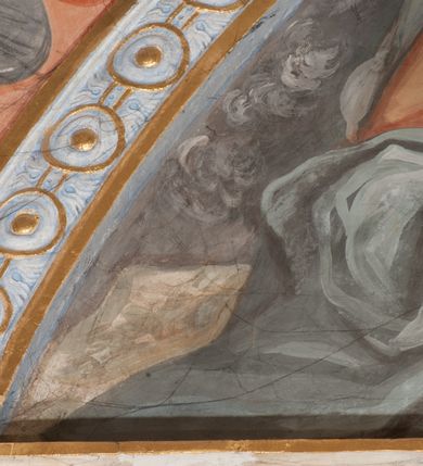 Zdjęcie nr 52: Iluzjonistyczną dekoracją malarską pokryto ściany kaplicy oraz strefę ponadcokołową: ściany tarczowe, pendentywy wokół stiukowych kartuszy herbowych oraz czaszę kopuły i wnętrze latarni. Ściany dolnej części podzielono na dwie strefy. Dolną tworzą zlokalizowane w narożach ścian iluzjonistycznie malowane pary nisz o konchach wypełnionych muszlą. W niszach ukazano osiem stojących frontalnie postaci starców, bez atrybutów i nimbów. Zapewne w ten sposób przedstawiono proroków lub apostołów. Każda z postaci ubrana jest w tunikę oraz płaszcz. Różnicuje je jedynie układ rąk, sposób kształtowania zarostu oraz kolorystyka szat. W drugiej strefie w przyłuczach arkad ukazano całopostaciowe przedstawienia uskrzydlonych aniołów trzymających narzędzia męki Pańskiej. Na ścianie wschodniej anioł prezentuje chustę Weroniki (z prawej) oraz latarnię (z lewej). Po bokach wejścia do kaplicy na ścianie północnej po prawej stronie anioł trzyma lancę i koronę cierniową, a po lewej krzyż. Z kolei na ścianie wschodniej po prawej ukazano anioła z drabiną, a po lewej z gąbką na trzcinie. Natomiast na ścianie południowej, po obu stronach zwieńczenia nagrobka, przedstawiono z prawej anioła z włócznią, a po lewej anioła z wiązką do biczowania. W tej strefie bezpośrednio przy łukach arkad wyobrażono leżące postacie geniuszy malowanych w technice en grisaille. Pod arkadą na ścianie wschodniej (ołtarzowej), ukazano dolną część owalnego jasno ugrowego baldachimu z lambrekinem i zielone, opadające paludamentum, rozsuwane kotarowo przez dwa uskrzydlone anioły. Dekoracja stanowi oprawę dla wiszącego tu obrazu Matki Boskiej z Dzieciątkiem w bogato rzeźbionej ramie. Z kolei na ścianie zachodniej wyobrażono monumentalną scenę Zdjęcia z krzyża. Jest to zwarta kompozycja ogniskująca się na wysokim drewnianym krzyżu, z którego ściągane jest martwe ciało Chrystusa. Z dwóch stron dłuższych ramion krzyż podtrzymują dwaj aniołowie. Ciało Jezusa opuszczane jest na białym pasie tkaniny przewiązanym pod jego ramionami. Chrystus ze zwisającą głową ma ręce ułożone wzdłuż ciała. Biodra przepasane ma białym perizonium. Jego skrzyżowane nogi są ugięte i jeszcze przybite gwoździem do krzyża. Gwóźdź wyciąga z nich obcęgami mężczyzna w niebieskiej, podwiniętej koszuli. Ciało opuszczają dwaj mężczyźni widoczni za poprzecznymi ramionami krzyża, trzymający końce taśmy. Człowiek z lewej strony w niebieskiej koszuli dodatkowo odbiera drugą białą taśmę od mężczyzny ubranego w szaroczarny strój. Osoba ta stoi na drabinie opartej o poprzeczne ramię krzyża. Drugi mężczyzna za krzyżem, w brązowej koszuli, lewą ręką trzyma koniec taśmy, a w uniesionej prawej młotek. Ciało Zbawiciela podtrzymuje lewą ręką kolejny mężczyzna stojący tyłem do widza na drugiej drabinie opartej o lewe ramię krzyża. Jest on ubrany w krótkie brązowe spodenki i bladozieloną koszulę. Pod krzyżem stoi zwarta siedmioosobowa grupa. Najprawdopodobniej z prawej strony ukazano św. Jana i Matkę Boską, na środku dwóch żołnierzy w ostro zakończonych hełmach, dwie kobiety, w tym zapewne Marię Magdalenę i starca widocznego z lewej strony kompozycji. Na ścianach tarczowych nad gzymsem wyobrażono po bokach okrągłych okien siedzących czterech ewangelistów i czterech ojców Kościoła. Na ścianie wschodniej znalazł się z prawej św. Jan z orłem, który w dziobie trzyma złoty kałamarz, a po lewej św. Mateusz rozmawiający z aniołem. Z kolei na ścianie południowej po lewej stronie przedstawiono św. Marka z lwem oraz św. Ambrożego trzymającego w prawej ręce naczynie z wylewającym się miodem. Na ścianie zachodniej z lewej znalazł się czytający św. Augustyn z sercem na dłoni, a z prawej św. Grzegorz Wielki z widoczną za nim tiarą i sową. Na ścianie północnej po lewej ukazano św. Hieronima z leżącym lwem, a po prawej stronie św. Łukasz z wołem. W pendentywach wykonano malarską dekorację w formie wijącej się wstęgi, na tle której widnieją stiukowe kartusze rollwerkowe, o owalnych kaboszonowych polach czwórdzielnych w krzyż. Po stronie wschodniej w pendentywach znajdują się dwa puste kartusze z niezachowanymi herbami. Natomiast herby zachowały się w pendentywach po stronie zachodniej. Na pendentywie północno-zachodnim: Jastrzębiec, Nowina, Gozdawa, Pobóg, a na południowo-zachodnim Gryf, Kotwicz, Kotwicz, Zabawa. W kopule wyobrażono Koronację Matki Boskiej adorowanej przez różnych świętych. Scenę koronacji Marii przez Trójcę Świętą przedstawiono w części wschodniej czaszy. Ukazana frontalnie Maria klęczy ze złożonymi rękami do modlitwy na obłokach. Ma owalną twarz okoloną jasnymi długimi włosami rozsypującymi się na jej ramiona. Na uniesionej ku górze głowie ma ubraną zsuwającą się białą chustę okrywającą włosy. Madonna ubrana jest w zasłaniający jej ramiona bladoniebieski płaszcz, opadający po bokach na obłoki. Nieznacznie wyżej z prawej strony na obłokach siedzi Bóg Ojciec. Wyobrażono go w trzech czwartych w prawo. Jest to starszy mężczyzna o siwych włosach i brodzie. W wyciągniętej prawej ręce nad głową Marii wraz z Chrystusem trzyma złotą koronę w typie zamkniętym. Z kolei w lewej podtrzymuje glob ze złotym krzyżykiem. Bóg Ojciec na głowie ma tiarę papieską. Ubrany jest w szaro-niebieską szatę oraz wzorzystą złotą kapę narzuconą na ramiona i spiętą pod szyją klamrą, z połami okrywającymi nogi. Naprzeciwko siedzi Chrystus widoczny w trzech czwartych w lewo z twarzą ukazaną w profilu. W wyciągniętej prawej ręce trzyma wraz z Bogiem Ojcem koronę, a lewą podtrzymuje złote berło. Chrystus ma jasne włosy opadające puklami na ramiona i podobną krótką brodę. Na głowie ma otwartą złotą koronę. Został przedstawiony z nagim torsem, na którym zaznaczono przebity bok. Jego postać otacza narzucony na ramiona bladoczerwony całun udrapowany w formie płaszcza. Nad koroną bliżej głowy Boga Ojca widoczna jest gołębica Ducha Świętego otoczona świetlistym otokiem. Ponad sceną koronacji wokół otworu do latarni wyobrażono wirujące złocisto-szare obłoki, na tle których widać uskrzydlone główki aniołków oraz postacie mniejszych i większych aniołków, które muzykują na różnych instrumentach, bądź też trzymają gałązki palmowe lub kwiaty albo kwiaty rozsypują. Uskrzydlone główki aniołków widoczne są także pośród obłoków, na których klęczy Madonna. Z prawej strony koronacji wyobrażono dwóch biskupów. Starszy, być może św. Wojciech, został przedstawiony w postawie półklęczącej w trzech czwartych w lewo. Prawą ręką zdaje się wskazywać na scenę koronacji, lewą zaś przyciska do piersi. Ma odkrytą głowę z widocznymi siwymi włosami i taką samą brodą. Ubrany jest w niebiesko-zielonkawą kapę ze złotym kapturem zakończonym chwostem. Na ziemi przy jego stopie widoczna jest złota infuła. Świętemu przyglądają się dwaj aniołowie widoczni z tyłu. Za nim klęczy młodszy biskup z leżącym przy nim na ziemi pastorałem i mieczem. Zapewne jest to św. Stanisław ze Szczepanowa. Święty ukazany został frontalnie z prawą ręką przyciśniętą do piersi, a z lewą nieznacznie odsuniętą w bok. Ma pociągłą twarz o krótkich jasnych włosach i podobnym zaroście. Ubrany jest w albę oraz szaro-bordową kapę o złotym kapturze. Przy jego kolanach stoi złota infuła, a za nim widoczny jest anioł z gałązką palmową. Za św. Stanisławem w rozwianych szatach klęczy św. Jadwiga Śląska, którą identyfikuje bryła kościoła widoczna przy jej stopach. Postać Jadwigi ukazano w profilu z założonymi rękami przed sobą. Na głowie ma niewielką złotą koronę, spod której widoczna jest biała chusta okrywająca włosy. Ubrana jest w bladoczerwoną suknię przepasaną w talii i narzucony na ramiona bladoszkarłatny płaszcz z gronostajowym kołnierzem i obszyciem. Za św. Jadwigą stoi inna święta z odsłoniętą lewą ręką wspartą o bok. Brak atrybutu nie pozwala na jej identyfikację. Ukazano ją w trzech czwartych w prawo z głową w profilu. Ma owalną twarz z wydatnym nosem. Na głowie ma niewielką złotą koronę, spod której widać jasną chustę okrywającą włosy. Ubrana jest w złocisto-szarą suknię z krótkimi rękawami i bladoczerwony rozwiany płaszcz. Pomiędzy obiema kobietami widać dwie postacie uskrzydlonych aniołów. Za świętymi siedzi z otwartą księgą wyobrażony frontalnie św. Jana Kanty. Jest to mężczyzna w średnim wieku z wysokim czołem, krótkimi brązowymi włosami i podobną brodą. Ubrany jest w bladofioletową togę akademicką z gronostajową peleryną. Trzymana przez niego księga ma czerwone okładki. Obok św. Jana Kantego namalowano czteroosobową grupę starszych mężczyzn. Pierwszy z nich, ujętych w trzech czwartych w prawo, zdaje się przyklękając, odbierać prawą ręką palmę męczeństwa podawaną mu przez widocznego nad nim anioła. Lewą ma ułożoną wzdłuż ciała. Ma podłużną twarz widoczną z profilu, otoczoną białymi włosami i spiczastą białą brodą. Ubrany jest w rozwianą jasnobeżową szatę przewiązaną w pasie i taki sam płaszcz narzucony na prawe ramię. Lewy rękaw tuniki jest podciągnięty, odsłaniając przedramię ręki. Na lewej nodze widoczny jest sandał. Za nim przedstawiono klęczącego w ujęciu trzech czwartych w lewo zakonnika eremitę, być może św. Pawła Pustelnika w białym habicie paulińskim. Zakonnik na wysokości bioder ma rozsunięte ręce. Jego twarz o wydatnym nosie otacza krzaczasta, długa, biała broda oraz białe włosy. W głębi za nim częściowo widać dwóch innych brodatych mężczyzn w beżowych szatach. Jeden z nich trzyma w dłoni palmę. W niewielkiej odległości za grupą mężczyzn na pierwszym planie klęczy na obłoku ukazany frontalnie św. Jacek. W rękach uniesionych na wysokości piersi trzyma wieżycową, złotą monstrancję i figurę Matki Boskiej. Dominikanin został przedstawiony z wysokim łysym czołem i wianuszkiem siwiejących włosów. Jego pociągła twarz o wyrazistym nosie i wąskich, nieznacznie zaciśniętych ustach pozbawiona jest zarostu. Ubrany jest w dominikański habit z czarnoniebieskim płaszczem. Z lewej strony sceny koronacji namalowano grupę czterech świętych. Na pierwszym planie widać klęczącego św. Stanisława Kostkę, wspartego na długim kiju z przywiązanym do niego węzełkiem. Święty został przedstawiony w profilu. Ma młodzieńczą, owalną twarz z krótkimi brązowymi włosami i rumianymi policzkami. Ubrany jest w bladobeżowy płaszcz, spod którego widać jasnoseledynową szatę. Za Stanisławem Kostką wyłania się w półpostaci św. Jan Nepomucen z drewnianym krzyżem podtrzymywanym lewą ręką. Jest to dojrzały mężczyzna o pociągłej twarzy, z brązowymi włosami i brodą. Z prawej strony św. Stanisława Kostki ukazano stojące dwie zakonnice, św. Kingę i zapewne bł. Salomeę. Kingę ukazano frontalnie w kontrapoście z głową uniesioną ku niebu w jasnobeżowym habicie klaryski wpadającym w brąz. Księżna prawą ręką przyciska do piersi bryłę soli, a w opuszczonej lewej trzyma kwiat lilii. U jej stóp widać model kościoła klasztornego w Starym Sączu. Obok stoi najprawdopodobniej bł. Salomea. Ukazano ją w mocnym kontrapoście, z dłońmi splecionymi na piersi i spojrzeniem skierowanym ku ziemi. Ubrana jest w rozwiany szaroniebieski habit i jasny welon. Wnętrze latarni wypełniają uskrzydlone głowy aniołków na tle złocisto-szarych obłoków.    







