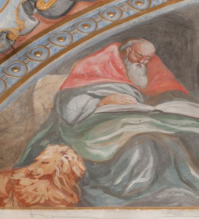 Zdjęcie nr 68: Iluzjonistyczną dekoracją malarską pokryto ściany kaplicy oraz strefę ponadcokołową: ściany tarczowe, pendentywy wokół stiukowych kartuszy herbowych oraz czaszę kopuły i wnętrze latarni. Ściany dolnej części podzielono na dwie strefy. Dolną tworzą zlokalizowane w narożach ścian iluzjonistycznie malowane pary nisz o konchach wypełnionych muszlą. W niszach ukazano osiem stojących frontalnie postaci starców, bez atrybutów i nimbów. Zapewne w ten sposób przedstawiono proroków lub apostołów. Każda z postaci ubrana jest w tunikę oraz płaszcz. Różnicuje je jedynie układ rąk, sposób kształtowania zarostu oraz kolorystyka szat. W drugiej strefie w przyłuczach arkad ukazano całopostaciowe przedstawienia uskrzydlonych aniołów trzymających narzędzia męki Pańskiej. Na ścianie wschodniej anioł prezentuje chustę Weroniki (z prawej) oraz latarnię (z lewej). Po bokach wejścia do kaplicy na ścianie północnej po prawej stronie anioł trzyma lancę i koronę cierniową, a po lewej krzyż. Z kolei na ścianie wschodniej po prawej ukazano anioła z drabiną, a po lewej z gąbką na trzcinie. Natomiast na ścianie południowej, po obu stronach zwieńczenia nagrobka, przedstawiono z prawej anioła z włócznią, a po lewej anioła z wiązką do biczowania. W tej strefie bezpośrednio przy łukach arkad wyobrażono leżące postacie geniuszy malowanych w technice en grisaille. Pod arkadą na ścianie wschodniej (ołtarzowej), ukazano dolną część owalnego jasno ugrowego baldachimu z lambrekinem i zielone, opadające paludamentum, rozsuwane kotarowo przez dwa uskrzydlone anioły. Dekoracja stanowi oprawę dla wiszącego tu obrazu Matki Boskiej z Dzieciątkiem w bogato rzeźbionej ramie. Z kolei na ścianie zachodniej wyobrażono monumentalną scenę Zdjęcia z krzyża. Jest to zwarta kompozycja ogniskująca się na wysokim drewnianym krzyżu, z którego ściągane jest martwe ciało Chrystusa. Z dwóch stron dłuższych ramion krzyż podtrzymują dwaj aniołowie. Ciało Jezusa opuszczane jest na białym pasie tkaniny przewiązanym pod jego ramionami. Chrystus ze zwisającą głową ma ręce ułożone wzdłuż ciała. Biodra przepasane ma białym perizonium. Jego skrzyżowane nogi są ugięte i jeszcze przybite gwoździem do krzyża. Gwóźdź wyciąga z nich obcęgami mężczyzna w niebieskiej, podwiniętej koszuli. Ciało opuszczają dwaj mężczyźni widoczni za poprzecznymi ramionami krzyża, trzymający końce taśmy. Człowiek z lewej strony w niebieskiej koszuli dodatkowo odbiera drugą białą taśmę od mężczyzny ubranego w szaroczarny strój. Osoba ta stoi na drabinie opartej o poprzeczne ramię krzyża. Drugi mężczyzna za krzyżem, w brązowej koszuli, lewą ręką trzyma koniec taśmy, a w uniesionej prawej młotek. Ciało Zbawiciela podtrzymuje lewą ręką kolejny mężczyzna stojący tyłem do widza na drugiej drabinie opartej o lewe ramię krzyża. Jest on ubrany w krótkie brązowe spodenki i bladozieloną koszulę. Pod krzyżem stoi zwarta siedmioosobowa grupa. Najprawdopodobniej z prawej strony ukazano św. Jana i Matkę Boską, na środku dwóch żołnierzy w ostro zakończonych hełmach, dwie kobiety, w tym zapewne Marię Magdalenę i starca widocznego z lewej strony kompozycji. Na ścianach tarczowych nad gzymsem wyobrażono po bokach okrągłych okien siedzących czterech ewangelistów i czterech ojców Kościoła. Na ścianie wschodniej znalazł się z prawej św. Jan z orłem, który w dziobie trzyma złoty kałamarz, a po lewej św. Mateusz rozmawiający z aniołem. Z kolei na ścianie południowej po lewej stronie przedstawiono św. Marka z lwem oraz św. Ambrożego trzymającego w prawej ręce naczynie z wylewającym się miodem. Na ścianie zachodniej z lewej znalazł się czytający św. Augustyn z sercem na dłoni, a z prawej św. Grzegorz Wielki z widoczną za nim tiarą i sową. Na ścianie północnej po lewej ukazano św. Hieronima z leżącym lwem, a po prawej stronie św. Łukasz z wołem. W pendentywach wykonano malarską dekorację w formie wijącej się wstęgi, na tle której widnieją stiukowe kartusze rollwerkowe, o owalnych kaboszonowych polach czwórdzielnych w krzyż. Po stronie wschodniej w pendentywach znajdują się dwa puste kartusze z niezachowanymi herbami. Natomiast herby zachowały się w pendentywach po stronie zachodniej. Na pendentywie północno-zachodnim: Jastrzębiec, Nowina, Gozdawa, Pobóg, a na południowo-zachodnim Gryf, Kotwicz, Kotwicz, Zabawa. W kopule wyobrażono Koronację Matki Boskiej adorowanej przez różnych świętych. Scenę koronacji Marii przez Trójcę Świętą przedstawiono w części wschodniej czaszy. Ukazana frontalnie Maria klęczy ze złożonymi rękami do modlitwy na obłokach. Ma owalną twarz okoloną jasnymi długimi włosami rozsypującymi się na jej ramiona. Na uniesionej ku górze głowie ma ubraną zsuwającą się białą chustę okrywającą włosy. Madonna ubrana jest w zasłaniający jej ramiona bladoniebieski płaszcz, opadający po bokach na obłoki. Nieznacznie wyżej z prawej strony na obłokach siedzi Bóg Ojciec. Wyobrażono go w trzech czwartych w prawo. Jest to starszy mężczyzna o siwych włosach i brodzie. W wyciągniętej prawej ręce nad głową Marii wraz z Chrystusem trzyma złotą koronę w typie zamkniętym. Z kolei w lewej podtrzymuje glob ze złotym krzyżykiem. Bóg Ojciec na głowie ma tiarę papieską. Ubrany jest w szaro-niebieską szatę oraz wzorzystą złotą kapę narzuconą na ramiona i spiętą pod szyją klamrą, z połami okrywającymi nogi. Naprzeciwko siedzi Chrystus widoczny w trzech czwartych w lewo z twarzą ukazaną w profilu. W wyciągniętej prawej ręce trzyma wraz z Bogiem Ojcem koronę, a lewą podtrzymuje złote berło. Chrystus ma jasne włosy opadające puklami na ramiona i podobną krótką brodę. Na głowie ma otwartą złotą koronę. Został przedstawiony z nagim torsem, na którym zaznaczono przebity bok. Jego postać otacza narzucony na ramiona bladoczerwony całun udrapowany w formie płaszcza. Nad koroną bliżej głowy Boga Ojca widoczna jest gołębica Ducha Świętego otoczona świetlistym otokiem. Ponad sceną koronacji wokół otworu do latarni wyobrażono wirujące złocisto-szare obłoki, na tle których widać uskrzydlone główki aniołków oraz postacie mniejszych i większych aniołków, które muzykują na różnych instrumentach, bądź też trzymają gałązki palmowe lub kwiaty albo kwiaty rozsypują. Uskrzydlone główki aniołków widoczne są także pośród obłoków, na których klęczy Madonna. Z prawej strony koronacji wyobrażono dwóch biskupów. Starszy, być może św. Wojciech, został przedstawiony w postawie półklęczącej w trzech czwartych w lewo. Prawą ręką zdaje się wskazywać na scenę koronacji, lewą zaś przyciska do piersi. Ma odkrytą głowę z widocznymi siwymi włosami i taką samą brodą. Ubrany jest w niebiesko-zielonkawą kapę ze złotym kapturem zakończonym chwostem. Na ziemi przy jego stopie widoczna jest złota infuła. Świętemu przyglądają się dwaj aniołowie widoczni z tyłu. Za nim klęczy młodszy biskup z leżącym przy nim na ziemi pastorałem i mieczem. Zapewne jest to św. Stanisław ze Szczepanowa. Święty ukazany został frontalnie z prawą ręką przyciśniętą do piersi, a z lewą nieznacznie odsuniętą w bok. Ma pociągłą twarz o krótkich jasnych włosach i podobnym zaroście. Ubrany jest w albę oraz szaro-bordową kapę o złotym kapturze. Przy jego kolanach stoi złota infuła, a za nim widoczny jest anioł z gałązką palmową. Za św. Stanisławem w rozwianych szatach klęczy św. Jadwiga Śląska, którą identyfikuje bryła kościoła widoczna przy jej stopach. Postać Jadwigi ukazano w profilu z założonymi rękami przed sobą. Na głowie ma niewielką złotą koronę, spod której widoczna jest biała chusta okrywająca włosy. Ubrana jest w bladoczerwoną suknię przepasaną w talii i narzucony na ramiona bladoszkarłatny płaszcz z gronostajowym kołnierzem i obszyciem. Za św. Jadwigą stoi inna święta z odsłoniętą lewą ręką wspartą o bok. Brak atrybutu nie pozwala na jej identyfikację. Ukazano ją w trzech czwartych w prawo z głową w profilu. Ma owalną twarz z wydatnym nosem. Na głowie ma niewielką złotą koronę, spod której widać jasną chustę okrywającą włosy. Ubrana jest w złocisto-szarą suknię z krótkimi rękawami i bladoczerwony rozwiany płaszcz. Pomiędzy obiema kobietami widać dwie postacie uskrzydlonych aniołów. Za świętymi siedzi z otwartą księgą wyobrażony frontalnie św. Jana Kanty. Jest to mężczyzna w średnim wieku z wysokim czołem, krótkimi brązowymi włosami i podobną brodą. Ubrany jest w bladofioletową togę akademicką z gronostajową peleryną. Trzymana przez niego księga ma czerwone okładki. Obok św. Jana Kantego namalowano czteroosobową grupę starszych mężczyzn. Pierwszy z nich, ujętych w trzech czwartych w prawo, zdaje się przyklękając, odbierać prawą ręką palmę męczeństwa podawaną mu przez widocznego nad nim anioła. Lewą ma ułożoną wzdłuż ciała. Ma podłużną twarz widoczną z profilu, otoczoną białymi włosami i spiczastą białą brodą. Ubrany jest w rozwianą jasnobeżową szatę przewiązaną w pasie i taki sam płaszcz narzucony na prawe ramię. Lewy rękaw tuniki jest podciągnięty, odsłaniając przedramię ręki. Na lewej nodze widoczny jest sandał. Za nim przedstawiono klęczącego w ujęciu trzech czwartych w lewo zakonnika eremitę, być może św. Pawła Pustelnika w białym habicie paulińskim. Zakonnik na wysokości bioder ma rozsunięte ręce. Jego twarz o wydatnym nosie otacza krzaczasta, długa, biała broda oraz białe włosy. W głębi za nim częściowo widać dwóch innych brodatych mężczyzn w beżowych szatach. Jeden z nich trzyma w dłoni palmę. W niewielkiej odległości za grupą mężczyzn na pierwszym planie klęczy na obłoku ukazany frontalnie św. Jacek. W rękach uniesionych na wysokości piersi trzyma wieżycową, złotą monstrancję i figurę Matki Boskiej. Dominikanin został przedstawiony z wysokim łysym czołem i wianuszkiem siwiejących włosów. Jego pociągła twarz o wyrazistym nosie i wąskich, nieznacznie zaciśniętych ustach pozbawiona jest zarostu. Ubrany jest w dominikański habit z czarnoniebieskim płaszczem. Z lewej strony sceny koronacji namalowano grupę czterech świętych. Na pierwszym planie widać klęczącego św. Stanisława Kostkę, wspartego na długim kiju z przywiązanym do niego węzełkiem. Święty został przedstawiony w profilu. Ma młodzieńczą, owalną twarz z krótkimi brązowymi włosami i rumianymi policzkami. Ubrany jest w bladobeżowy płaszcz, spod którego widać jasnoseledynową szatę. Za Stanisławem Kostką wyłania się w półpostaci św. Jan Nepomucen z drewnianym krzyżem podtrzymywanym lewą ręką. Jest to dojrzały mężczyzna o pociągłej twarzy, z brązowymi włosami i brodą. Z prawej strony św. Stanisława Kostki ukazano stojące dwie zakonnice, św. Kingę i zapewne bł. Salomeę. Kingę ukazano frontalnie w kontrapoście z głową uniesioną ku niebu w jasnobeżowym habicie klaryski wpadającym w brąz. Księżna prawą ręką przyciska do piersi bryłę soli, a w opuszczonej lewej trzyma kwiat lilii. U jej stóp widać model kościoła klasztornego w Starym Sączu. Obok stoi najprawdopodobniej bł. Salomea. Ukazano ją w mocnym kontrapoście, z dłońmi splecionymi na piersi i spojrzeniem skierowanym ku ziemi. Ubrana jest w rozwiany szaroniebieski habit i jasny welon. Wnętrze latarni wypełniają uskrzydlone głowy aniołków na tle złocisto-szarych obłoków.    







