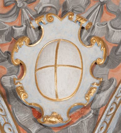 Zdjęcie nr 70: Iluzjonistyczną dekoracją malarską pokryto ściany kaplicy oraz strefę ponadcokołową: ściany tarczowe, pendentywy wokół stiukowych kartuszy herbowych oraz czaszę kopuły i wnętrze latarni. Ściany dolnej części podzielono na dwie strefy. Dolną tworzą zlokalizowane w narożach ścian iluzjonistycznie malowane pary nisz o konchach wypełnionych muszlą. W niszach ukazano osiem stojących frontalnie postaci starców, bez atrybutów i nimbów. Zapewne w ten sposób przedstawiono proroków lub apostołów. Każda z postaci ubrana jest w tunikę oraz płaszcz. Różnicuje je jedynie układ rąk, sposób kształtowania zarostu oraz kolorystyka szat. W drugiej strefie w przyłuczach arkad ukazano całopostaciowe przedstawienia uskrzydlonych aniołów trzymających narzędzia męki Pańskiej. Na ścianie wschodniej anioł prezentuje chustę Weroniki (z prawej) oraz latarnię (z lewej). Po bokach wejścia do kaplicy na ścianie północnej po prawej stronie anioł trzyma lancę i koronę cierniową, a po lewej krzyż. Z kolei na ścianie wschodniej po prawej ukazano anioła z drabiną, a po lewej z gąbką na trzcinie. Natomiast na ścianie południowej, po obu stronach zwieńczenia nagrobka, przedstawiono z prawej anioła z włócznią, a po lewej anioła z wiązką do biczowania. W tej strefie bezpośrednio przy łukach arkad wyobrażono leżące postacie geniuszy malowanych w technice en grisaille. Pod arkadą na ścianie wschodniej (ołtarzowej), ukazano dolną część owalnego jasno ugrowego baldachimu z lambrekinem i zielone, opadające paludamentum, rozsuwane kotarowo przez dwa uskrzydlone anioły. Dekoracja stanowi oprawę dla wiszącego tu obrazu Matki Boskiej z Dzieciątkiem w bogato rzeźbionej ramie. Z kolei na ścianie zachodniej wyobrażono monumentalną scenę Zdjęcia z krzyża. Jest to zwarta kompozycja ogniskująca się na wysokim drewnianym krzyżu, z którego ściągane jest martwe ciało Chrystusa. Z dwóch stron dłuższych ramion krzyż podtrzymują dwaj aniołowie. Ciało Jezusa opuszczane jest na białym pasie tkaniny przewiązanym pod jego ramionami. Chrystus ze zwisającą głową ma ręce ułożone wzdłuż ciała. Biodra przepasane ma białym perizonium. Jego skrzyżowane nogi są ugięte i jeszcze przybite gwoździem do krzyża. Gwóźdź wyciąga z nich obcęgami mężczyzna w niebieskiej, podwiniętej koszuli. Ciało opuszczają dwaj mężczyźni widoczni za poprzecznymi ramionami krzyża, trzymający końce taśmy. Człowiek z lewej strony w niebieskiej koszuli dodatkowo odbiera drugą białą taśmę od mężczyzny ubranego w szaroczarny strój. Osoba ta stoi na drabinie opartej o poprzeczne ramię krzyża. Drugi mężczyzna za krzyżem, w brązowej koszuli, lewą ręką trzyma koniec taśmy, a w uniesionej prawej młotek. Ciało Zbawiciela podtrzymuje lewą ręką kolejny mężczyzna stojący tyłem do widza na drugiej drabinie opartej o lewe ramię krzyża. Jest on ubrany w krótkie brązowe spodenki i bladozieloną koszulę. Pod krzyżem stoi zwarta siedmioosobowa grupa. Najprawdopodobniej z prawej strony ukazano św. Jana i Matkę Boską, na środku dwóch żołnierzy w ostro zakończonych hełmach, dwie kobiety, w tym zapewne Marię Magdalenę i starca widocznego z lewej strony kompozycji. Na ścianach tarczowych nad gzymsem wyobrażono po bokach okrągłych okien siedzących czterech ewangelistów i czterech ojców Kościoła. Na ścianie wschodniej znalazł się z prawej św. Jan z orłem, który w dziobie trzyma złoty kałamarz, a po lewej św. Mateusz rozmawiający z aniołem. Z kolei na ścianie południowej po lewej stronie przedstawiono św. Marka z lwem oraz św. Ambrożego trzymającego w prawej ręce naczynie z wylewającym się miodem. Na ścianie zachodniej z lewej znalazł się czytający św. Augustyn z sercem na dłoni, a z prawej św. Grzegorz Wielki z widoczną za nim tiarą i sową. Na ścianie północnej po lewej ukazano św. Hieronima z leżącym lwem, a po prawej stronie św. Łukasz z wołem. W pendentywach wykonano malarską dekorację w formie wijącej się wstęgi, na tle której widnieją stiukowe kartusze rollwerkowe, o owalnych kaboszonowych polach czwórdzielnych w krzyż. Po stronie wschodniej w pendentywach znajdują się dwa puste kartusze z niezachowanymi herbami. Natomiast herby zachowały się w pendentywach po stronie zachodniej. Na pendentywie północno-zachodnim: Jastrzębiec, Nowina, Gozdawa, Pobóg, a na południowo-zachodnim Gryf, Kotwicz, Kotwicz, Zabawa. W kopule wyobrażono Koronację Matki Boskiej adorowanej przez różnych świętych. Scenę koronacji Marii przez Trójcę Świętą przedstawiono w części wschodniej czaszy. Ukazana frontalnie Maria klęczy ze złożonymi rękami do modlitwy na obłokach. Ma owalną twarz okoloną jasnymi długimi włosami rozsypującymi się na jej ramiona. Na uniesionej ku górze głowie ma ubraną zsuwającą się białą chustę okrywającą włosy. Madonna ubrana jest w zasłaniający jej ramiona bladoniebieski płaszcz, opadający po bokach na obłoki. Nieznacznie wyżej z prawej strony na obłokach siedzi Bóg Ojciec. Wyobrażono go w trzech czwartych w prawo. Jest to starszy mężczyzna o siwych włosach i brodzie. W wyciągniętej prawej ręce nad głową Marii wraz z Chrystusem trzyma złotą koronę w typie zamkniętym. Z kolei w lewej podtrzymuje glob ze złotym krzyżykiem. Bóg Ojciec na głowie ma tiarę papieską. Ubrany jest w szaro-niebieską szatę oraz wzorzystą złotą kapę narzuconą na ramiona i spiętą pod szyją klamrą, z połami okrywającymi nogi. Naprzeciwko siedzi Chrystus widoczny w trzech czwartych w lewo z twarzą ukazaną w profilu. W wyciągniętej prawej ręce trzyma wraz z Bogiem Ojcem koronę, a lewą podtrzymuje złote berło. Chrystus ma jasne włosy opadające puklami na ramiona i podobną krótką brodę. Na głowie ma otwartą złotą koronę. Został przedstawiony z nagim torsem, na którym zaznaczono przebity bok. Jego postać otacza narzucony na ramiona bladoczerwony całun udrapowany w formie płaszcza. Nad koroną bliżej głowy Boga Ojca widoczna jest gołębica Ducha Świętego otoczona świetlistym otokiem. Ponad sceną koronacji wokół otworu do latarni wyobrażono wirujące złocisto-szare obłoki, na tle których widać uskrzydlone główki aniołków oraz postacie mniejszych i większych aniołków, które muzykują na różnych instrumentach, bądź też trzymają gałązki palmowe lub kwiaty albo kwiaty rozsypują. Uskrzydlone główki aniołków widoczne są także pośród obłoków, na których klęczy Madonna. Z prawej strony koronacji wyobrażono dwóch biskupów. Starszy, być może św. Wojciech, został przedstawiony w postawie półklęczącej w trzech czwartych w lewo. Prawą ręką zdaje się wskazywać na scenę koronacji, lewą zaś przyciska do piersi. Ma odkrytą głowę z widocznymi siwymi włosami i taką samą brodą. Ubrany jest w niebiesko-zielonkawą kapę ze złotym kapturem zakończonym chwostem. Na ziemi przy jego stopie widoczna jest złota infuła. Świętemu przyglądają się dwaj aniołowie widoczni z tyłu. Za nim klęczy młodszy biskup z leżącym przy nim na ziemi pastorałem i mieczem. Zapewne jest to św. Stanisław ze Szczepanowa. Święty ukazany został frontalnie z prawą ręką przyciśniętą do piersi, a z lewą nieznacznie odsuniętą w bok. Ma pociągłą twarz o krótkich jasnych włosach i podobnym zaroście. Ubrany jest w albę oraz szaro-bordową kapę o złotym kapturze. Przy jego kolanach stoi złota infuła, a za nim widoczny jest anioł z gałązką palmową. Za św. Stanisławem w rozwianych szatach klęczy św. Jadwiga Śląska, którą identyfikuje bryła kościoła widoczna przy jej stopach. Postać Jadwigi ukazano w profilu z założonymi rękami przed sobą. Na głowie ma niewielką złotą koronę, spod której widoczna jest biała chusta okrywająca włosy. Ubrana jest w bladoczerwoną suknię przepasaną w talii i narzucony na ramiona bladoszkarłatny płaszcz z gronostajowym kołnierzem i obszyciem. Za św. Jadwigą stoi inna święta z odsłoniętą lewą ręką wspartą o bok. Brak atrybutu nie pozwala na jej identyfikację. Ukazano ją w trzech czwartych w prawo z głową w profilu. Ma owalną twarz z wydatnym nosem. Na głowie ma niewielką złotą koronę, spod której widać jasną chustę okrywającą włosy. Ubrana jest w złocisto-szarą suknię z krótkimi rękawami i bladoczerwony rozwiany płaszcz. Pomiędzy obiema kobietami widać dwie postacie uskrzydlonych aniołów. Za świętymi siedzi z otwartą księgą wyobrażony frontalnie św. Jana Kanty. Jest to mężczyzna w średnim wieku z wysokim czołem, krótkimi brązowymi włosami i podobną brodą. Ubrany jest w bladofioletową togę akademicką z gronostajową peleryną. Trzymana przez niego księga ma czerwone okładki. Obok św. Jana Kantego namalowano czteroosobową grupę starszych mężczyzn. Pierwszy z nich, ujętych w trzech czwartych w prawo, zdaje się przyklękając, odbierać prawą ręką palmę męczeństwa podawaną mu przez widocznego nad nim anioła. Lewą ma ułożoną wzdłuż ciała. Ma podłużną twarz widoczną z profilu, otoczoną białymi włosami i spiczastą białą brodą. Ubrany jest w rozwianą jasnobeżową szatę przewiązaną w pasie i taki sam płaszcz narzucony na prawe ramię. Lewy rękaw tuniki jest podciągnięty, odsłaniając przedramię ręki. Na lewej nodze widoczny jest sandał. Za nim przedstawiono klęczącego w ujęciu trzech czwartych w lewo zakonnika eremitę, być może św. Pawła Pustelnika w białym habicie paulińskim. Zakonnik na wysokości bioder ma rozsunięte ręce. Jego twarz o wydatnym nosie otacza krzaczasta, długa, biała broda oraz białe włosy. W głębi za nim częściowo widać dwóch innych brodatych mężczyzn w beżowych szatach. Jeden z nich trzyma w dłoni palmę. W niewielkiej odległości za grupą mężczyzn na pierwszym planie klęczy na obłoku ukazany frontalnie św. Jacek. W rękach uniesionych na wysokości piersi trzyma wieżycową, złotą monstrancję i figurę Matki Boskiej. Dominikanin został przedstawiony z wysokim łysym czołem i wianuszkiem siwiejących włosów. Jego pociągła twarz o wyrazistym nosie i wąskich, nieznacznie zaciśniętych ustach pozbawiona jest zarostu. Ubrany jest w dominikański habit z czarnoniebieskim płaszczem. Z lewej strony sceny koronacji namalowano grupę czterech świętych. Na pierwszym planie widać klęczącego św. Stanisława Kostkę, wspartego na długim kiju z przywiązanym do niego węzełkiem. Święty został przedstawiony w profilu. Ma młodzieńczą, owalną twarz z krótkimi brązowymi włosami i rumianymi policzkami. Ubrany jest w bladobeżowy płaszcz, spod którego widać jasnoseledynową szatę. Za Stanisławem Kostką wyłania się w półpostaci św. Jan Nepomucen z drewnianym krzyżem podtrzymywanym lewą ręką. Jest to dojrzały mężczyzna o pociągłej twarzy, z brązowymi włosami i brodą. Z prawej strony św. Stanisława Kostki ukazano stojące dwie zakonnice, św. Kingę i zapewne bł. Salomeę. Kingę ukazano frontalnie w kontrapoście z głową uniesioną ku niebu w jasnobeżowym habicie klaryski wpadającym w brąz. Księżna prawą ręką przyciska do piersi bryłę soli, a w opuszczonej lewej trzyma kwiat lilii. U jej stóp widać model kościoła klasztornego w Starym Sączu. Obok stoi najprawdopodobniej bł. Salomea. Ukazano ją w mocnym kontrapoście, z dłońmi splecionymi na piersi i spojrzeniem skierowanym ku ziemi. Ubrana jest w rozwiany szaroniebieski habit i jasny welon. Wnętrze latarni wypełniają uskrzydlone głowy aniołków na tle złocisto-szarych obłoków.    








