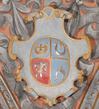 Zdjęcie nr 71: Iluzjonistyczną dekoracją malarską pokryto ściany kaplicy oraz strefę ponadcokołową: ściany tarczowe, pendentywy wokół stiukowych kartuszy herbowych oraz czaszę kopuły i wnętrze latarni. Ściany dolnej części podzielono na dwie strefy. Dolną tworzą zlokalizowane w narożach ścian iluzjonistycznie malowane pary nisz o konchach wypełnionych muszlą. W niszach ukazano osiem stojących frontalnie postaci starców, bez atrybutów i nimbów. Zapewne w ten sposób przedstawiono proroków lub apostołów. Każda z postaci ubrana jest w tunikę oraz płaszcz. Różnicuje je jedynie układ rąk, sposób kształtowania zarostu oraz kolorystyka szat. W drugiej strefie w przyłuczach arkad ukazano całopostaciowe przedstawienia uskrzydlonych aniołów trzymających narzędzia męki Pańskiej. Na ścianie wschodniej anioł prezentuje chustę Weroniki (z prawej) oraz latarnię (z lewej). Po bokach wejścia do kaplicy na ścianie północnej po prawej stronie anioł trzyma lancę i koronę cierniową, a po lewej krzyż. Z kolei na ścianie wschodniej po prawej ukazano anioła z drabiną, a po lewej z gąbką na trzcinie. Natomiast na ścianie południowej, po obu stronach zwieńczenia nagrobka, przedstawiono z prawej anioła z włócznią, a po lewej anioła z wiązką do biczowania. W tej strefie bezpośrednio przy łukach arkad wyobrażono leżące postacie geniuszy malowanych w technice en grisaille. Pod arkadą na ścianie wschodniej (ołtarzowej), ukazano dolną część owalnego jasno ugrowego baldachimu z lambrekinem i zielone, opadające paludamentum, rozsuwane kotarowo przez dwa uskrzydlone anioły. Dekoracja stanowi oprawę dla wiszącego tu obrazu Matki Boskiej z Dzieciątkiem w bogato rzeźbionej ramie. Z kolei na ścianie zachodniej wyobrażono monumentalną scenę Zdjęcia z krzyża. Jest to zwarta kompozycja ogniskująca się na wysokim drewnianym krzyżu, z którego ściągane jest martwe ciało Chrystusa. Z dwóch stron dłuższych ramion krzyż podtrzymują dwaj aniołowie. Ciało Jezusa opuszczane jest na białym pasie tkaniny przewiązanym pod jego ramionami. Chrystus ze zwisającą głową ma ręce ułożone wzdłuż ciała. Biodra przepasane ma białym perizonium. Jego skrzyżowane nogi są ugięte i jeszcze przybite gwoździem do krzyża. Gwóźdź wyciąga z nich obcęgami mężczyzna w niebieskiej, podwiniętej koszuli. Ciało opuszczają dwaj mężczyźni widoczni za poprzecznymi ramionami krzyża, trzymający końce taśmy. Człowiek z lewej strony w niebieskiej koszuli dodatkowo odbiera drugą białą taśmę od mężczyzny ubranego w szaroczarny strój. Osoba ta stoi na drabinie opartej o poprzeczne ramię krzyża. Drugi mężczyzna za krzyżem, w brązowej koszuli, lewą ręką trzyma koniec taśmy, a w uniesionej prawej młotek. Ciało Zbawiciela podtrzymuje lewą ręką kolejny mężczyzna stojący tyłem do widza na drugiej drabinie opartej o lewe ramię krzyża. Jest on ubrany w krótkie brązowe spodenki i bladozieloną koszulę. Pod krzyżem stoi zwarta siedmioosobowa grupa. Najprawdopodobniej z prawej strony ukazano św. Jana i Matkę Boską, na środku dwóch żołnierzy w ostro zakończonych hełmach, dwie kobiety, w tym zapewne Marię Magdalenę i starca widocznego z lewej strony kompozycji. Na ścianach tarczowych nad gzymsem wyobrażono po bokach okrągłych okien siedzących czterech ewangelistów i czterech ojców Kościoła. Na ścianie wschodniej znalazł się z prawej św. Jan z orłem, który w dziobie trzyma złoty kałamarz, a po lewej św. Mateusz rozmawiający z aniołem. Z kolei na ścianie południowej po lewej stronie przedstawiono św. Marka z lwem oraz św. Ambrożego trzymającego w prawej ręce naczynie z wylewającym się miodem. Na ścianie zachodniej z lewej znalazł się czytający św. Augustyn z sercem na dłoni, a z prawej św. Grzegorz Wielki z widoczną za nim tiarą i sową. Na ścianie północnej po lewej ukazano św. Hieronima z leżącym lwem, a po prawej stronie św. Łukasz z wołem. W pendentywach wykonano malarską dekorację w formie wijącej się wstęgi, na tle której widnieją stiukowe kartusze rollwerkowe, o owalnych kaboszonowych polach czwórdzielnych w krzyż. Po stronie wschodniej w pendentywach znajdują się dwa puste kartusze z niezachowanymi herbami. Natomiast herby zachowały się w pendentywach po stronie zachodniej. Na pendentywie północno-zachodnim: Jastrzębiec, Nowina, Gozdawa, Pobóg, a na południowo-zachodnim Gryf, Kotwicz, Kotwicz, Zabawa. W kopule wyobrażono Koronację Matki Boskiej adorowanej przez różnych świętych. Scenę koronacji Marii przez Trójcę Świętą przedstawiono w części wschodniej czaszy. Ukazana frontalnie Maria klęczy ze złożonymi rękami do modlitwy na obłokach. Ma owalną twarz okoloną jasnymi długimi włosami rozsypującymi się na jej ramiona. Na uniesionej ku górze głowie ma ubraną zsuwającą się białą chustę okrywającą włosy. Madonna ubrana jest w zasłaniający jej ramiona bladoniebieski płaszcz, opadający po bokach na obłoki. Nieznacznie wyżej z prawej strony na obłokach siedzi Bóg Ojciec. Wyobrażono go w trzech czwartych w prawo. Jest to starszy mężczyzna o siwych włosach i brodzie. W wyciągniętej prawej ręce nad głową Marii wraz z Chrystusem trzyma złotą koronę w typie zamkniętym. Z kolei w lewej podtrzymuje glob ze złotym krzyżykiem. Bóg Ojciec na głowie ma tiarę papieską. Ubrany jest w szaro-niebieską szatę oraz wzorzystą złotą kapę narzuconą na ramiona i spiętą pod szyją klamrą, z połami okrywającymi nogi. Naprzeciwko siedzi Chrystus widoczny w trzech czwartych w lewo z twarzą ukazaną w profilu. W wyciągniętej prawej ręce trzyma wraz z Bogiem Ojcem koronę, a lewą podtrzymuje złote berło. Chrystus ma jasne włosy opadające puklami na ramiona i podobną krótką brodę. Na głowie ma otwartą złotą koronę. Został przedstawiony z nagim torsem, na którym zaznaczono przebity bok. Jego postać otacza narzucony na ramiona bladoczerwony całun udrapowany w formie płaszcza. Nad koroną bliżej głowy Boga Ojca widoczna jest gołębica Ducha Świętego otoczona świetlistym otokiem. Ponad sceną koronacji wokół otworu do latarni wyobrażono wirujące złocisto-szare obłoki, na tle których widać uskrzydlone główki aniołków oraz postacie mniejszych i większych aniołków, które muzykują na różnych instrumentach, bądź też trzymają gałązki palmowe lub kwiaty albo kwiaty rozsypują. Uskrzydlone główki aniołków widoczne są także pośród obłoków, na których klęczy Madonna. Z prawej strony koronacji wyobrażono dwóch biskupów. Starszy, być może św. Wojciech, został przedstawiony w postawie półklęczącej w trzech czwartych w lewo. Prawą ręką zdaje się wskazywać na scenę koronacji, lewą zaś przyciska do piersi. Ma odkrytą głowę z widocznymi siwymi włosami i taką samą brodą. Ubrany jest w niebiesko-zielonkawą kapę ze złotym kapturem zakończonym chwostem. Na ziemi przy jego stopie widoczna jest złota infuła. Świętemu przyglądają się dwaj aniołowie widoczni z tyłu. Za nim klęczy młodszy biskup z leżącym przy nim na ziemi pastorałem i mieczem. Zapewne jest to św. Stanisław ze Szczepanowa. Święty ukazany został frontalnie z prawą ręką przyciśniętą do piersi, a z lewą nieznacznie odsuniętą w bok. Ma pociągłą twarz o krótkich jasnych włosach i podobnym zaroście. Ubrany jest w albę oraz szaro-bordową kapę o złotym kapturze. Przy jego kolanach stoi złota infuła, a za nim widoczny jest anioł z gałązką palmową. Za św. Stanisławem w rozwianych szatach klęczy św. Jadwiga Śląska, którą identyfikuje bryła kościoła widoczna przy jej stopach. Postać Jadwigi ukazano w profilu z założonymi rękami przed sobą. Na głowie ma niewielką złotą koronę, spod której widoczna jest biała chusta okrywająca włosy. Ubrana jest w bladoczerwoną suknię przepasaną w talii i narzucony na ramiona bladoszkarłatny płaszcz z gronostajowym kołnierzem i obszyciem. Za św. Jadwigą stoi inna święta z odsłoniętą lewą ręką wspartą o bok. Brak atrybutu nie pozwala na jej identyfikację. Ukazano ją w trzech czwartych w prawo z głową w profilu. Ma owalną twarz z wydatnym nosem. Na głowie ma niewielką złotą koronę, spod której widać jasną chustę okrywającą włosy. Ubrana jest w złocisto-szarą suknię z krótkimi rękawami i bladoczerwony rozwiany płaszcz. Pomiędzy obiema kobietami widać dwie postacie uskrzydlonych aniołów. Za świętymi siedzi z otwartą księgą wyobrażony frontalnie św. Jana Kanty. Jest to mężczyzna w średnim wieku z wysokim czołem, krótkimi brązowymi włosami i podobną brodą. Ubrany jest w bladofioletową togę akademicką z gronostajową peleryną. Trzymana przez niego księga ma czerwone okładki. Obok św. Jana Kantego namalowano czteroosobową grupę starszych mężczyzn. Pierwszy z nich, ujętych w trzech czwartych w prawo, zdaje się przyklękając, odbierać prawą ręką palmę męczeństwa podawaną mu przez widocznego nad nim anioła. Lewą ma ułożoną wzdłuż ciała. Ma podłużną twarz widoczną z profilu, otoczoną białymi włosami i spiczastą białą brodą. Ubrany jest w rozwianą jasnobeżową szatę przewiązaną w pasie i taki sam płaszcz narzucony na prawe ramię. Lewy rękaw tuniki jest podciągnięty, odsłaniając przedramię ręki. Na lewej nodze widoczny jest sandał. Za nim przedstawiono klęczącego w ujęciu trzech czwartych w lewo zakonnika eremitę, być może św. Pawła Pustelnika w białym habicie paulińskim. Zakonnik na wysokości bioder ma rozsunięte ręce. Jego twarz o wydatnym nosie otacza krzaczasta, długa, biała broda oraz białe włosy. W głębi za nim częściowo widać dwóch innych brodatych mężczyzn w beżowych szatach. Jeden z nich trzyma w dłoni palmę. W niewielkiej odległości za grupą mężczyzn na pierwszym planie klęczy na obłoku ukazany frontalnie św. Jacek. W rękach uniesionych na wysokości piersi trzyma wieżycową, złotą monstrancję i figurę Matki Boskiej. Dominikanin został przedstawiony z wysokim łysym czołem i wianuszkiem siwiejących włosów. Jego pociągła twarz o wyrazistym nosie i wąskich, nieznacznie zaciśniętych ustach pozbawiona jest zarostu. Ubrany jest w dominikański habit z czarnoniebieskim płaszczem. Z lewej strony sceny koronacji namalowano grupę czterech świętych. Na pierwszym planie widać klęczącego św. Stanisława Kostkę, wspartego na długim kiju z przywiązanym do niego węzełkiem. Święty został przedstawiony w profilu. Ma młodzieńczą, owalną twarz z krótkimi brązowymi włosami i rumianymi policzkami. Ubrany jest w bladobeżowy płaszcz, spod którego widać jasnoseledynową szatę. Za Stanisławem Kostką wyłania się w półpostaci św. Jan Nepomucen z drewnianym krzyżem podtrzymywanym lewą ręką. Jest to dojrzały mężczyzna o pociągłej twarzy, z brązowymi włosami i brodą. Z prawej strony św. Stanisława Kostki ukazano stojące dwie zakonnice, św. Kingę i zapewne bł. Salomeę. Kingę ukazano frontalnie w kontrapoście z głową uniesioną ku niebu w jasnobeżowym habicie klaryski wpadającym w brąz. Księżna prawą ręką przyciska do piersi bryłę soli, a w opuszczonej lewej trzyma kwiat lilii. U jej stóp widać model kościoła klasztornego w Starym Sączu. Obok stoi najprawdopodobniej bł. Salomea. Ukazano ją w mocnym kontrapoście, z dłońmi splecionymi na piersi i spojrzeniem skierowanym ku ziemi. Ubrana jest w rozwiany szaroniebieski habit i jasny welon. Wnętrze latarni wypełniają uskrzydlone głowy aniołków na tle złocisto-szarych obłoków.    







