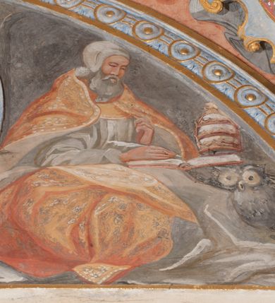 Zdjęcie nr 77: Iluzjonistyczną dekoracją malarską pokryto ściany kaplicy oraz strefę ponadcokołową: ściany tarczowe, pendentywy wokół stiukowych kartuszy herbowych oraz czaszę kopuły i wnętrze latarni. Ściany dolnej części podzielono na dwie strefy. Dolną tworzą zlokalizowane w narożach ścian iluzjonistycznie malowane pary nisz o konchach wypełnionych muszlą. W niszach ukazano osiem stojących frontalnie postaci starców, bez atrybutów i nimbów. Zapewne w ten sposób przedstawiono proroków lub apostołów. Każda z postaci ubrana jest w tunikę oraz płaszcz. Różnicuje je jedynie układ rąk, sposób kształtowania zarostu oraz kolorystyka szat. W drugiej strefie w przyłuczach arkad ukazano całopostaciowe przedstawienia uskrzydlonych aniołów trzymających narzędzia męki Pańskiej. Na ścianie wschodniej anioł prezentuje chustę Weroniki (z prawej) oraz latarnię (z lewej). Po bokach wejścia do kaplicy na ścianie północnej po prawej stronie anioł trzyma lancę i koronę cierniową, a po lewej krzyż. Z kolei na ścianie wschodniej po prawej ukazano anioła z drabiną, a po lewej z gąbką na trzcinie. Natomiast na ścianie południowej, po obu stronach zwieńczenia nagrobka, przedstawiono z prawej anioła z włócznią, a po lewej anioła z wiązką do biczowania. W tej strefie bezpośrednio przy łukach arkad wyobrażono leżące postacie geniuszy malowanych w technice en grisaille. Pod arkadą na ścianie wschodniej (ołtarzowej), ukazano dolną część owalnego jasno ugrowego baldachimu z lambrekinem i zielone, opadające paludamentum, rozsuwane kotarowo przez dwa uskrzydlone anioły. Dekoracja stanowi oprawę dla wiszącego tu obrazu Matki Boskiej z Dzieciątkiem w bogato rzeźbionej ramie. Z kolei na ścianie zachodniej wyobrażono monumentalną scenę Zdjęcia z krzyża. Jest to zwarta kompozycja ogniskująca się na wysokim drewnianym krzyżu, z którego ściągane jest martwe ciało Chrystusa. Z dwóch stron dłuższych ramion krzyż podtrzymują dwaj aniołowie. Ciało Jezusa opuszczane jest na białym pasie tkaniny przewiązanym pod jego ramionami. Chrystus ze zwisającą głową ma ręce ułożone wzdłuż ciała. Biodra przepasane ma białym perizonium. Jego skrzyżowane nogi są ugięte i jeszcze przybite gwoździem do krzyża. Gwóźdź wyciąga z nich obcęgami mężczyzna w niebieskiej, podwiniętej koszuli. Ciało opuszczają dwaj mężczyźni widoczni za poprzecznymi ramionami krzyża, trzymający końce taśmy. Człowiek z lewej strony w niebieskiej koszuli dodatkowo odbiera drugą białą taśmę od mężczyzny ubranego w szaroczarny strój. Osoba ta stoi na drabinie opartej o poprzeczne ramię krzyża. Drugi mężczyzna za krzyżem, w brązowej koszuli, lewą ręką trzyma koniec taśmy, a w uniesionej prawej młotek. Ciało Zbawiciela podtrzymuje lewą ręką kolejny mężczyzna stojący tyłem do widza na drugiej drabinie opartej o lewe ramię krzyża. Jest on ubrany w krótkie brązowe spodenki i bladozieloną koszulę. Pod krzyżem stoi zwarta siedmioosobowa grupa. Najprawdopodobniej z prawej strony ukazano św. Jana i Matkę Boską, na środku dwóch żołnierzy w ostro zakończonych hełmach, dwie kobiety, w tym zapewne Marię Magdalenę i starca widocznego z lewej strony kompozycji. Na ścianach tarczowych nad gzymsem wyobrażono po bokach okrągłych okien siedzących czterech ewangelistów i czterech ojców Kościoła. Na ścianie wschodniej znalazł się z prawej św. Jan z orłem, który w dziobie trzyma złoty kałamarz, a po lewej św. Mateusz rozmawiający z aniołem. Z kolei na ścianie południowej po lewej stronie przedstawiono św. Marka z lwem oraz św. Ambrożego trzymającego w prawej ręce naczynie z wylewającym się miodem. Na ścianie zachodniej z lewej znalazł się czytający św. Augustyn z sercem na dłoni, a z prawej św. Grzegorz Wielki z widoczną za nim tiarą i sową. Na ścianie północnej po lewej ukazano św. Hieronima z leżącym lwem, a po prawej stronie św. Łukasz z wołem. W pendentywach wykonano malarską dekorację w formie wijącej się wstęgi, na tle której widnieją stiukowe kartusze rollwerkowe, o owalnych kaboszonowych polach czwórdzielnych w krzyż. Po stronie wschodniej w pendentywach znajdują się dwa puste kartusze z niezachowanymi herbami. Natomiast herby zachowały się w pendentywach po stronie zachodniej. Na pendentywie północno-zachodnim: Jastrzębiec, Nowina, Gozdawa, Pobóg, a na południowo-zachodnim Gryf, Kotwicz, Kotwicz, Zabawa. W kopule wyobrażono Koronację Matki Boskiej adorowanej przez różnych świętych. Scenę koronacji Marii przez Trójcę Świętą przedstawiono w części wschodniej czaszy. Ukazana frontalnie Maria klęczy ze złożonymi rękami do modlitwy na obłokach. Ma owalną twarz okoloną jasnymi długimi włosami rozsypującymi się na jej ramiona. Na uniesionej ku górze głowie ma ubraną zsuwającą się białą chustę okrywającą włosy. Madonna ubrana jest w zasłaniający jej ramiona bladoniebieski płaszcz, opadający po bokach na obłoki. Nieznacznie wyżej z prawej strony na obłokach siedzi Bóg Ojciec. Wyobrażono go w trzech czwartych w prawo. Jest to starszy mężczyzna o siwych włosach i brodzie. W wyciągniętej prawej ręce nad głową Marii wraz z Chrystusem trzyma złotą koronę w typie zamkniętym. Z kolei w lewej podtrzymuje glob ze złotym krzyżykiem. Bóg Ojciec na głowie ma tiarę papieską. Ubrany jest w szaro-niebieską szatę oraz wzorzystą złotą kapę narzuconą na ramiona i spiętą pod szyją klamrą, z połami okrywającymi nogi. Naprzeciwko siedzi Chrystus widoczny w trzech czwartych w lewo z twarzą ukazaną w profilu. W wyciągniętej prawej ręce trzyma wraz z Bogiem Ojcem koronę, a lewą podtrzymuje złote berło. Chrystus ma jasne włosy opadające puklami na ramiona i podobną krótką brodę. Na głowie ma otwartą złotą koronę. Został przedstawiony z nagim torsem, na którym zaznaczono przebity bok. Jego postać otacza narzucony na ramiona bladoczerwony całun udrapowany w formie płaszcza. Nad koroną bliżej głowy Boga Ojca widoczna jest gołębica Ducha Świętego otoczona świetlistym otokiem. Ponad sceną koronacji wokół otworu do latarni wyobrażono wirujące złocisto-szare obłoki, na tle których widać uskrzydlone główki aniołków oraz postacie mniejszych i większych aniołków, które muzykują na różnych instrumentach, bądź też trzymają gałązki palmowe lub kwiaty albo kwiaty rozsypują. Uskrzydlone główki aniołków widoczne są także pośród obłoków, na których klęczy Madonna. Z prawej strony koronacji wyobrażono dwóch biskupów. Starszy, być może św. Wojciech, został przedstawiony w postawie półklęczącej w trzech czwartych w lewo. Prawą ręką zdaje się wskazywać na scenę koronacji, lewą zaś przyciska do piersi. Ma odkrytą głowę z widocznymi siwymi włosami i taką samą brodą. Ubrany jest w niebiesko-zielonkawą kapę ze złotym kapturem zakończonym chwostem. Na ziemi przy jego stopie widoczna jest złota infuła. Świętemu przyglądają się dwaj aniołowie widoczni z tyłu. Za nim klęczy młodszy biskup z leżącym przy nim na ziemi pastorałem i mieczem. Zapewne jest to św. Stanisław ze Szczepanowa. Święty ukazany został frontalnie z prawą ręką przyciśniętą do piersi, a z lewą nieznacznie odsuniętą w bok. Ma pociągłą twarz o krótkich jasnych włosach i podobnym zaroście. Ubrany jest w albę oraz szaro-bordową kapę o złotym kapturze. Przy jego kolanach stoi złota infuła, a za nim widoczny jest anioł z gałązką palmową. Za św. Stanisławem w rozwianych szatach klęczy św. Jadwiga Śląska, którą identyfikuje bryła kościoła widoczna przy jej stopach. Postać Jadwigi ukazano w profilu z założonymi rękami przed sobą. Na głowie ma niewielką złotą koronę, spod której widoczna jest biała chusta okrywająca włosy. Ubrana jest w bladoczerwoną suknię przepasaną w talii i narzucony na ramiona bladoszkarłatny płaszcz z gronostajowym kołnierzem i obszyciem. Za św. Jadwigą stoi inna święta z odsłoniętą lewą ręką wspartą o bok. Brak atrybutu nie pozwala na jej identyfikację. Ukazano ją w trzech czwartych w prawo z głową w profilu. Ma owalną twarz z wydatnym nosem. Na głowie ma niewielką złotą koronę, spod której widać jasną chustę okrywającą włosy. Ubrana jest w złocisto-szarą suknię z krótkimi rękawami i bladoczerwony rozwiany płaszcz. Pomiędzy obiema kobietami widać dwie postacie uskrzydlonych aniołów. Za świętymi siedzi z otwartą księgą wyobrażony frontalnie św. Jana Kanty. Jest to mężczyzna w średnim wieku z wysokim czołem, krótkimi brązowymi włosami i podobną brodą. Ubrany jest w bladofioletową togę akademicką z gronostajową peleryną. Trzymana przez niego księga ma czerwone okładki. Obok św. Jana Kantego namalowano czteroosobową grupę starszych mężczyzn. Pierwszy z nich, ujętych w trzech czwartych w prawo, zdaje się przyklękając, odbierać prawą ręką palmę męczeństwa podawaną mu przez widocznego nad nim anioła. Lewą ma ułożoną wzdłuż ciała. Ma podłużną twarz widoczną z profilu, otoczoną białymi włosami i spiczastą białą brodą. Ubrany jest w rozwianą jasnobeżową szatę przewiązaną w pasie i taki sam płaszcz narzucony na prawe ramię. Lewy rękaw tuniki jest podciągnięty, odsłaniając przedramię ręki. Na lewej nodze widoczny jest sandał. Za nim przedstawiono klęczącego w ujęciu trzech czwartych w lewo zakonnika eremitę, być może św. Pawła Pustelnika w białym habicie paulińskim. Zakonnik na wysokości bioder ma rozsunięte ręce. Jego twarz o wydatnym nosie otacza krzaczasta, długa, biała broda oraz białe włosy. W głębi za nim częściowo widać dwóch innych brodatych mężczyzn w beżowych szatach. Jeden z nich trzyma w dłoni palmę. W niewielkiej odległości za grupą mężczyzn na pierwszym planie klęczy na obłoku ukazany frontalnie św. Jacek. W rękach uniesionych na wysokości piersi trzyma wieżycową, złotą monstrancję i figurę Matki Boskiej. Dominikanin został przedstawiony z wysokim łysym czołem i wianuszkiem siwiejących włosów. Jego pociągła twarz o wyrazistym nosie i wąskich, nieznacznie zaciśniętych ustach pozbawiona jest zarostu. Ubrany jest w dominikański habit z czarnoniebieskim płaszczem. Z lewej strony sceny koronacji namalowano grupę czterech świętych. Na pierwszym planie widać klęczącego św. Stanisława Kostkę, wspartego na długim kiju z przywiązanym do niego węzełkiem. Święty został przedstawiony w profilu. Ma młodzieńczą, owalną twarz z krótkimi brązowymi włosami i rumianymi policzkami. Ubrany jest w bladobeżowy płaszcz, spod którego widać jasnoseledynową szatę. Za Stanisławem Kostką wyłania się w półpostaci św. Jan Nepomucen z drewnianym krzyżem podtrzymywanym lewą ręką. Jest to dojrzały mężczyzna o pociągłej twarzy, z brązowymi włosami i brodą. Z prawej strony św. Stanisława Kostki ukazano stojące dwie zakonnice, św. Kingę i zapewne bł. Salomeę. Kingę ukazano frontalnie w kontrapoście z głową uniesioną ku niebu w jasnobeżowym habicie klaryski wpadającym w brąz. Księżna prawą ręką przyciska do piersi bryłę soli, a w opuszczonej lewej trzyma kwiat lilii. U jej stóp widać model kościoła klasztornego w Starym Sączu. Obok stoi najprawdopodobniej bł. Salomea. Ukazano ją w mocnym kontrapoście, z dłońmi splecionymi na piersi i spojrzeniem skierowanym ku ziemi. Ubrana jest w rozwiany szaroniebieski habit i jasny welon. Wnętrze latarni wypełniają uskrzydlone głowy aniołków na tle złocisto-szarych obłoków.    







