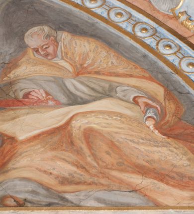 Zdjęcie nr 90: Iluzjonistyczną dekoracją malarską pokryto ściany kaplicy oraz strefę ponadcokołową: ściany tarczowe, pendentywy wokół stiukowych kartuszy herbowych oraz czaszę kopuły i wnętrze latarni. Ściany dolnej części podzielono na dwie strefy. Dolną tworzą zlokalizowane w narożach ścian iluzjonistycznie malowane pary nisz o konchach wypełnionych muszlą. W niszach ukazano osiem stojących frontalnie postaci starców, bez atrybutów i nimbów. Zapewne w ten sposób przedstawiono proroków lub apostołów. Każda z postaci ubrana jest w tunikę oraz płaszcz. Różnicuje je jedynie układ rąk, sposób kształtowania zarostu oraz kolorystyka szat. W drugiej strefie w przyłuczach arkad ukazano całopostaciowe przedstawienia uskrzydlonych aniołów trzymających narzędzia męki Pańskiej. Na ścianie wschodniej anioł prezentuje chustę Weroniki (z prawej) oraz latarnię (z lewej). Po bokach wejścia do kaplicy na ścianie północnej po prawej stronie anioł trzyma lancę i koronę cierniową, a po lewej krzyż. Z kolei na ścianie wschodniej po prawej ukazano anioła z drabiną, a po lewej z gąbką na trzcinie. Natomiast na ścianie południowej, po obu stronach zwieńczenia nagrobka, przedstawiono z prawej anioła z włócznią, a po lewej anioła z wiązką do biczowania. W tej strefie bezpośrednio przy łukach arkad wyobrażono leżące postacie geniuszy malowanych w technice en grisaille. Pod arkadą na ścianie wschodniej (ołtarzowej), ukazano dolną część owalnego jasno ugrowego baldachimu z lambrekinem i zielone, opadające paludamentum, rozsuwane kotarowo przez dwa uskrzydlone anioły. Dekoracja stanowi oprawę dla wiszącego tu obrazu Matki Boskiej z Dzieciątkiem w bogato rzeźbionej ramie. Z kolei na ścianie zachodniej wyobrażono monumentalną scenę Zdjęcia z krzyża. Jest to zwarta kompozycja ogniskująca się na wysokim drewnianym krzyżu, z którego ściągane jest martwe ciało Chrystusa. Z dwóch stron dłuższych ramion krzyż podtrzymują dwaj aniołowie. Ciało Jezusa opuszczane jest na białym pasie tkaniny przewiązanym pod jego ramionami. Chrystus ze zwisającą głową ma ręce ułożone wzdłuż ciała. Biodra przepasane ma białym perizonium. Jego skrzyżowane nogi są ugięte i jeszcze przybite gwoździem do krzyża. Gwóźdź wyciąga z nich obcęgami mężczyzna w niebieskiej, podwiniętej koszuli. Ciało opuszczają dwaj mężczyźni widoczni za poprzecznymi ramionami krzyża, trzymający końce taśmy. Człowiek z lewej strony w niebieskiej koszuli dodatkowo odbiera drugą białą taśmę od mężczyzny ubranego w szaroczarny strój. Osoba ta stoi na drabinie opartej o poprzeczne ramię krzyża. Drugi mężczyzna za krzyżem, w brązowej koszuli, lewą ręką trzyma koniec taśmy, a w uniesionej prawej młotek. Ciało Zbawiciela podtrzymuje lewą ręką kolejny mężczyzna stojący tyłem do widza na drugiej drabinie opartej o lewe ramię krzyża. Jest on ubrany w krótkie brązowe spodenki i bladozieloną koszulę. Pod krzyżem stoi zwarta siedmioosobowa grupa. Najprawdopodobniej z prawej strony ukazano św. Jana i Matkę Boską, na środku dwóch żołnierzy w ostro zakończonych hełmach, dwie kobiety, w tym zapewne Marię Magdalenę i starca widocznego z lewej strony kompozycji. Na ścianach tarczowych nad gzymsem wyobrażono po bokach okrągłych okien siedzących czterech ewangelistów i czterech ojców Kościoła. Na ścianie wschodniej znalazł się z prawej św. Jan z orłem, który w dziobie trzyma złoty kałamarz, a po lewej św. Mateusz rozmawiający z aniołem. Z kolei na ścianie południowej po lewej stronie przedstawiono św. Marka z lwem oraz św. Ambrożego trzymającego w prawej ręce naczynie z wylewającym się miodem. Na ścianie zachodniej z lewej znalazł się czytający św. Augustyn z sercem na dłoni, a z prawej św. Grzegorz Wielki z widoczną za nim tiarą i sową. Na ścianie północnej po lewej ukazano św. Hieronima z leżącym lwem, a po prawej stronie św. Łukasz z wołem. W pendentywach wykonano malarską dekorację w formie wijącej się wstęgi, na tle której widnieją stiukowe kartusze rollwerkowe, o owalnych kaboszonowych polach czwórdzielnych w krzyż. Po stronie wschodniej w pendentywach znajdują się dwa puste kartusze z niezachowanymi herbami. Natomiast herby zachowały się w pendentywach po stronie zachodniej. Na pendentywie północno-zachodnim: Jastrzębiec, Nowina, Gozdawa, Pobóg, a na południowo-zachodnim Gryf, Kotwicz, Kotwicz, Zabawa. W kopule wyobrażono Koronację Matki Boskiej adorowanej przez różnych świętych. Scenę koronacji Marii przez Trójcę Świętą przedstawiono w części wschodniej czaszy. Ukazana frontalnie Maria klęczy ze złożonymi rękami do modlitwy na obłokach. Ma owalną twarz okoloną jasnymi długimi włosami rozsypującymi się na jej ramiona. Na uniesionej ku górze głowie ma ubraną zsuwającą się białą chustę okrywającą włosy. Madonna ubrana jest w zasłaniający jej ramiona bladoniebieski płaszcz, opadający po bokach na obłoki. Nieznacznie wyżej z prawej strony na obłokach siedzi Bóg Ojciec. Wyobrażono go w trzech czwartych w prawo. Jest to starszy mężczyzna o siwych włosach i brodzie. W wyciągniętej prawej ręce nad głową Marii wraz z Chrystusem trzyma złotą koronę w typie zamkniętym. Z kolei w lewej podtrzymuje glob ze złotym krzyżykiem. Bóg Ojciec na głowie ma tiarę papieską. Ubrany jest w szaro-niebieską szatę oraz wzorzystą złotą kapę narzuconą na ramiona i spiętą pod szyją klamrą, z połami okrywającymi nogi. Naprzeciwko siedzi Chrystus widoczny w trzech czwartych w lewo z twarzą ukazaną w profilu. W wyciągniętej prawej ręce trzyma wraz z Bogiem Ojcem koronę, a lewą podtrzymuje złote berło. Chrystus ma jasne włosy opadające puklami na ramiona i podobną krótką brodę. Na głowie ma otwartą złotą koronę. Został przedstawiony z nagim torsem, na którym zaznaczono przebity bok. Jego postać otacza narzucony na ramiona bladoczerwony całun udrapowany w formie płaszcza. Nad koroną bliżej głowy Boga Ojca widoczna jest gołębica Ducha Świętego otoczona świetlistym otokiem. Ponad sceną koronacji wokół otworu do latarni wyobrażono wirujące złocisto-szare obłoki, na tle których widać uskrzydlone główki aniołków oraz postacie mniejszych i większych aniołków, które muzykują na różnych instrumentach, bądź też trzymają gałązki palmowe lub kwiaty albo kwiaty rozsypują. Uskrzydlone główki aniołków widoczne są także pośród obłoków, na których klęczy Madonna. Z prawej strony koronacji wyobrażono dwóch biskupów. Starszy, być może św. Wojciech, został przedstawiony w postawie półklęczącej w trzech czwartych w lewo. Prawą ręką zdaje się wskazywać na scenę koronacji, lewą zaś przyciska do piersi. Ma odkrytą głowę z widocznymi siwymi włosami i taką samą brodą. Ubrany jest w niebiesko-zielonkawą kapę ze złotym kapturem zakończonym chwostem. Na ziemi przy jego stopie widoczna jest złota infuła. Świętemu przyglądają się dwaj aniołowie widoczni z tyłu. Za nim klęczy młodszy biskup z leżącym przy nim na ziemi pastorałem i mieczem. Zapewne jest to św. Stanisław ze Szczepanowa. Święty ukazany został frontalnie z prawą ręką przyciśniętą do piersi, a z lewą nieznacznie odsuniętą w bok. Ma pociągłą twarz o krótkich jasnych włosach i podobnym zaroście. Ubrany jest w albę oraz szaro-bordową kapę o złotym kapturze. Przy jego kolanach stoi złota infuła, a za nim widoczny jest anioł z gałązką palmową. Za św. Stanisławem w rozwianych szatach klęczy św. Jadwiga Śląska, którą identyfikuje bryła kościoła widoczna przy jej stopach. Postać Jadwigi ukazano w profilu z założonymi rękami przed sobą. Na głowie ma niewielką złotą koronę, spod której widoczna jest biała chusta okrywająca włosy. Ubrana jest w bladoczerwoną suknię przepasaną w talii i narzucony na ramiona bladoszkarłatny płaszcz z gronostajowym kołnierzem i obszyciem. Za św. Jadwigą stoi inna święta z odsłoniętą lewą ręką wspartą o bok. Brak atrybutu nie pozwala na jej identyfikację. Ukazano ją w trzech czwartych w prawo z głową w profilu. Ma owalną twarz z wydatnym nosem. Na głowie ma niewielką złotą koronę, spod której widać jasną chustę okrywającą włosy. Ubrana jest w złocisto-szarą suknię z krótkimi rękawami i bladoczerwony rozwiany płaszcz. Pomiędzy obiema kobietami widać dwie postacie uskrzydlonych aniołów. Za świętymi siedzi z otwartą księgą wyobrażony frontalnie św. Jana Kanty. Jest to mężczyzna w średnim wieku z wysokim czołem, krótkimi brązowymi włosami i podobną brodą. Ubrany jest w bladofioletową togę akademicką z gronostajową peleryną. Trzymana przez niego księga ma czerwone okładki. Obok św. Jana Kantego namalowano czteroosobową grupę starszych mężczyzn. Pierwszy z nich, ujętych w trzech czwartych w prawo, zdaje się przyklękając, odbierać prawą ręką palmę męczeństwa podawaną mu przez widocznego nad nim anioła. Lewą ma ułożoną wzdłuż ciała. Ma podłużną twarz widoczną z profilu, otoczoną białymi włosami i spiczastą białą brodą. Ubrany jest w rozwianą jasnobeżową szatę przewiązaną w pasie i taki sam płaszcz narzucony na prawe ramię. Lewy rękaw tuniki jest podciągnięty, odsłaniając przedramię ręki. Na lewej nodze widoczny jest sandał. Za nim przedstawiono klęczącego w ujęciu trzech czwartych w lewo zakonnika eremitę, być może św. Pawła Pustelnika w białym habicie paulińskim. Zakonnik na wysokości bioder ma rozsunięte ręce. Jego twarz o wydatnym nosie otacza krzaczasta, długa, biała broda oraz białe włosy. W głębi za nim częściowo widać dwóch innych brodatych mężczyzn w beżowych szatach. Jeden z nich trzyma w dłoni palmę. W niewielkiej odległości za grupą mężczyzn na pierwszym planie klęczy na obłoku ukazany frontalnie św. Jacek. W rękach uniesionych na wysokości piersi trzyma wieżycową, złotą monstrancję i figurę Matki Boskiej. Dominikanin został przedstawiony z wysokim łysym czołem i wianuszkiem siwiejących włosów. Jego pociągła twarz o wyrazistym nosie i wąskich, nieznacznie zaciśniętych ustach pozbawiona jest zarostu. Ubrany jest w dominikański habit z czarnoniebieskim płaszczem. Z lewej strony sceny koronacji namalowano grupę czterech świętych. Na pierwszym planie widać klęczącego św. Stanisława Kostkę, wspartego na długim kiju z przywiązanym do niego węzełkiem. Święty został przedstawiony w profilu. Ma młodzieńczą, owalną twarz z krótkimi brązowymi włosami i rumianymi policzkami. Ubrany jest w bladobeżowy płaszcz, spod którego widać jasnoseledynową szatę. Za Stanisławem Kostką wyłania się w półpostaci św. Jan Nepomucen z drewnianym krzyżem podtrzymywanym lewą ręką. Jest to dojrzały mężczyzna o pociągłej twarzy, z brązowymi włosami i brodą. Z prawej strony św. Stanisława Kostki ukazano stojące dwie zakonnice, św. Kingę i zapewne bł. Salomeę. Kingę ukazano frontalnie w kontrapoście z głową uniesioną ku niebu w jasnobeżowym habicie klaryski wpadającym w brąz. Księżna prawą ręką przyciska do piersi bryłę soli, a w opuszczonej lewej trzyma kwiat lilii. U jej stóp widać model kościoła klasztornego w Starym Sączu. Obok stoi najprawdopodobniej bł. Salomea. Ukazano ją w mocnym kontrapoście, z dłońmi splecionymi na piersi i spojrzeniem skierowanym ku ziemi. Ubrana jest w rozwiany szaroniebieski habit i jasny welon. Wnętrze latarni wypełniają uskrzydlone głowy aniołków na tle złocisto-szarych obłoków.    







