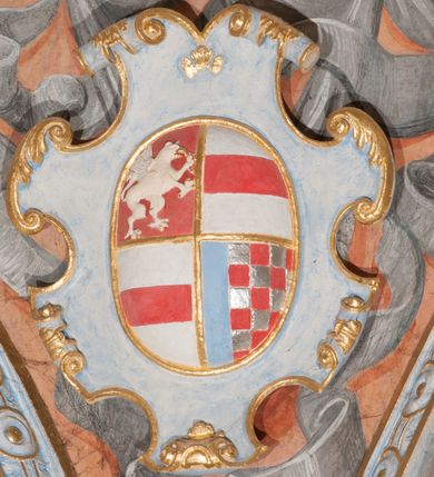 Zdjęcie nr 95: Iluzjonistyczną dekoracją malarską pokryto ściany kaplicy oraz strefę ponadcokołową: ściany tarczowe, pendentywy wokół stiukowych kartuszy herbowych oraz czaszę kopuły i wnętrze latarni. Ściany dolnej części podzielono na dwie strefy. Dolną tworzą zlokalizowane w narożach ścian iluzjonistycznie malowane pary nisz o konchach wypełnionych muszlą. W niszach ukazano osiem stojących frontalnie postaci starców, bez atrybutów i nimbów. Zapewne w ten sposób przedstawiono proroków lub apostołów. Każda z postaci ubrana jest w tunikę oraz płaszcz. Różnicuje je jedynie układ rąk, sposób kształtowania zarostu oraz kolorystyka szat. W drugiej strefie w przyłuczach arkad ukazano całopostaciowe przedstawienia uskrzydlonych aniołów trzymających narzędzia męki Pańskiej. Na ścianie wschodniej anioł prezentuje chustę Weroniki (z prawej) oraz latarnię (z lewej). Po bokach wejścia do kaplicy na ścianie północnej po prawej stronie anioł trzyma lancę i koronę cierniową, a po lewej krzyż. Z kolei na ścianie wschodniej po prawej ukazano anioła z drabiną, a po lewej z gąbką na trzcinie. Natomiast na ścianie południowej, po obu stronach zwieńczenia nagrobka, przedstawiono z prawej anioła z włócznią, a po lewej anioła z wiązką do biczowania. W tej strefie bezpośrednio przy łukach arkad wyobrażono leżące postacie geniuszy malowanych w technice en grisaille. Pod arkadą na ścianie wschodniej (ołtarzowej), ukazano dolną część owalnego jasno ugrowego baldachimu z lambrekinem i zielone, opadające paludamentum, rozsuwane kotarowo przez dwa uskrzydlone anioły. Dekoracja stanowi oprawę dla wiszącego tu obrazu Matki Boskiej z Dzieciątkiem w bogato rzeźbionej ramie. Z kolei na ścianie zachodniej wyobrażono monumentalną scenę Zdjęcia z krzyża. Jest to zwarta kompozycja ogniskująca się na wysokim drewnianym krzyżu, z którego ściągane jest martwe ciało Chrystusa. Z dwóch stron dłuższych ramion krzyż podtrzymują dwaj aniołowie. Ciało Jezusa opuszczane jest na białym pasie tkaniny przewiązanym pod jego ramionami. Chrystus ze zwisającą głową ma ręce ułożone wzdłuż ciała. Biodra przepasane ma białym perizonium. Jego skrzyżowane nogi są ugięte i jeszcze przybite gwoździem do krzyża. Gwóźdź wyciąga z nich obcęgami mężczyzna w niebieskiej, podwiniętej koszuli. Ciało opuszczają dwaj mężczyźni widoczni za poprzecznymi ramionami krzyża, trzymający końce taśmy. Człowiek z lewej strony w niebieskiej koszuli dodatkowo odbiera drugą białą taśmę od mężczyzny ubranego w szaroczarny strój. Osoba ta stoi na drabinie opartej o poprzeczne ramię krzyża. Drugi mężczyzna za krzyżem, w brązowej koszuli, lewą ręką trzyma koniec taśmy, a w uniesionej prawej młotek. Ciało Zbawiciela podtrzymuje lewą ręką kolejny mężczyzna stojący tyłem do widza na drugiej drabinie opartej o lewe ramię krzyża. Jest on ubrany w krótkie brązowe spodenki i bladozieloną koszulę. Pod krzyżem stoi zwarta siedmioosobowa grupa. Najprawdopodobniej z prawej strony ukazano św. Jana i Matkę Boską, na środku dwóch żołnierzy w ostro zakończonych hełmach, dwie kobiety, w tym zapewne Marię Magdalenę i starca widocznego z lewej strony kompozycji. Na ścianach tarczowych nad gzymsem wyobrażono po bokach okrągłych okien siedzących czterech ewangelistów i czterech ojców Kościoła. Na ścianie wschodniej znalazł się z prawej św. Jan z orłem, który w dziobie trzyma złoty kałamarz, a po lewej św. Mateusz rozmawiający z aniołem. Z kolei na ścianie południowej po lewej stronie przedstawiono św. Marka z lwem oraz św. Ambrożego trzymającego w prawej ręce naczynie z wylewającym się miodem. Na ścianie zachodniej z lewej znalazł się czytający św. Augustyn z sercem na dłoni, a z prawej św. Grzegorz Wielki z widoczną za nim tiarą i sową. Na ścianie północnej po lewej ukazano św. Hieronima z leżącym lwem, a po prawej stronie św. Łukasz z wołem. W pendentywach wykonano malarską dekorację w formie wijącej się wstęgi, na tle której widnieją stiukowe kartusze rollwerkowe, o owalnych kaboszonowych polach czwórdzielnych w krzyż. Po stronie wschodniej w pendentywach znajdują się dwa puste kartusze z niezachowanymi herbami. Natomiast herby zachowały się w pendentywach po stronie zachodniej. Na pendentywie północno-zachodnim: Jastrzębiec, Nowina, Gozdawa, Pobóg, a na południowo-zachodnim Gryf, Kotwicz, Kotwicz, Zabawa. W kopule wyobrażono Koronację Matki Boskiej adorowanej przez różnych świętych. Scenę koronacji Marii przez Trójcę Świętą przedstawiono w części wschodniej czaszy. Ukazana frontalnie Maria klęczy ze złożonymi rękami do modlitwy na obłokach. Ma owalną twarz okoloną jasnymi długimi włosami rozsypującymi się na jej ramiona. Na uniesionej ku górze głowie ma ubraną zsuwającą się białą chustę okrywającą włosy. Madonna ubrana jest w zasłaniający jej ramiona bladoniebieski płaszcz, opadający po bokach na obłoki. Nieznacznie wyżej z prawej strony na obłokach siedzi Bóg Ojciec. Wyobrażono go w trzech czwartych w prawo. Jest to starszy mężczyzna o siwych włosach i brodzie. W wyciągniętej prawej ręce nad głową Marii wraz z Chrystusem trzyma złotą koronę w typie zamkniętym. Z kolei w lewej podtrzymuje glob ze złotym krzyżykiem. Bóg Ojciec na głowie ma tiarę papieską. Ubrany jest w szaro-niebieską szatę oraz wzorzystą złotą kapę narzuconą na ramiona i spiętą pod szyją klamrą, z połami okrywającymi nogi. Naprzeciwko siedzi Chrystus widoczny w trzech czwartych w lewo z twarzą ukazaną w profilu. W wyciągniętej prawej ręce trzyma wraz z Bogiem Ojcem koronę, a lewą podtrzymuje złote berło. Chrystus ma jasne włosy opadające puklami na ramiona i podobną krótką brodę. Na głowie ma otwartą złotą koronę. Został przedstawiony z nagim torsem, na którym zaznaczono przebity bok. Jego postać otacza narzucony na ramiona bladoczerwony całun udrapowany w formie płaszcza. Nad koroną bliżej głowy Boga Ojca widoczna jest gołębica Ducha Świętego otoczona świetlistym otokiem. Ponad sceną koronacji wokół otworu do latarni wyobrażono wirujące złocisto-szare obłoki, na tle których widać uskrzydlone główki aniołków oraz postacie mniejszych i większych aniołków, które muzykują na różnych instrumentach, bądź też trzymają gałązki palmowe lub kwiaty albo kwiaty rozsypują. Uskrzydlone główki aniołków widoczne są także pośród obłoków, na których klęczy Madonna. Z prawej strony koronacji wyobrażono dwóch biskupów. Starszy, być może św. Wojciech, został przedstawiony w postawie półklęczącej w trzech czwartych w lewo. Prawą ręką zdaje się wskazywać na scenę koronacji, lewą zaś przyciska do piersi. Ma odkrytą głowę z widocznymi siwymi włosami i taką samą brodą. Ubrany jest w niebiesko-zielonkawą kapę ze złotym kapturem zakończonym chwostem. Na ziemi przy jego stopie widoczna jest złota infuła. Świętemu przyglądają się dwaj aniołowie widoczni z tyłu. Za nim klęczy młodszy biskup z leżącym przy nim na ziemi pastorałem i mieczem. Zapewne jest to św. Stanisław ze Szczepanowa. Święty ukazany został frontalnie z prawą ręką przyciśniętą do piersi, a z lewą nieznacznie odsuniętą w bok. Ma pociągłą twarz o krótkich jasnych włosach i podobnym zaroście. Ubrany jest w albę oraz szaro-bordową kapę o złotym kapturze. Przy jego kolanach stoi złota infuła, a za nim widoczny jest anioł z gałązką palmową. Za św. Stanisławem w rozwianych szatach klęczy św. Jadwiga Śląska, którą identyfikuje bryła kościoła widoczna przy jej stopach. Postać Jadwigi ukazano w profilu z założonymi rękami przed sobą. Na głowie ma niewielką złotą koronę, spod której widoczna jest biała chusta okrywająca włosy. Ubrana jest w bladoczerwoną suknię przepasaną w talii i narzucony na ramiona bladoszkarłatny płaszcz z gronostajowym kołnierzem i obszyciem. Za św. Jadwigą stoi inna święta z odsłoniętą lewą ręką wspartą o bok. Brak atrybutu nie pozwala na jej identyfikację. Ukazano ją w trzech czwartych w prawo z głową w profilu. Ma owalną twarz z wydatnym nosem. Na głowie ma niewielką złotą koronę, spod której widać jasną chustę okrywającą włosy. Ubrana jest w złocisto-szarą suknię z krótkimi rękawami i bladoczerwony rozwiany płaszcz. Pomiędzy obiema kobietami widać dwie postacie uskrzydlonych aniołów. Za świętymi siedzi z otwartą księgą wyobrażony frontalnie św. Jana Kanty. Jest to mężczyzna w średnim wieku z wysokim czołem, krótkimi brązowymi włosami i podobną brodą. Ubrany jest w bladofioletową togę akademicką z gronostajową peleryną. Trzymana przez niego księga ma czerwone okładki. Obok św. Jana Kantego namalowano czteroosobową grupę starszych mężczyzn. Pierwszy z nich, ujętych w trzech czwartych w prawo, zdaje się przyklękając, odbierać prawą ręką palmę męczeństwa podawaną mu przez widocznego nad nim anioła. Lewą ma ułożoną wzdłuż ciała. Ma podłużną twarz widoczną z profilu, otoczoną białymi włosami i spiczastą białą brodą. Ubrany jest w rozwianą jasnobeżową szatę przewiązaną w pasie i taki sam płaszcz narzucony na prawe ramię. Lewy rękaw tuniki jest podciągnięty, odsłaniając przedramię ręki. Na lewej nodze widoczny jest sandał. Za nim przedstawiono klęczącego w ujęciu trzech czwartych w lewo zakonnika eremitę, być może św. Pawła Pustelnika w białym habicie paulińskim. Zakonnik na wysokości bioder ma rozsunięte ręce. Jego twarz o wydatnym nosie otacza krzaczasta, długa, biała broda oraz białe włosy. W głębi za nim częściowo widać dwóch innych brodatych mężczyzn w beżowych szatach. Jeden z nich trzyma w dłoni palmę. W niewielkiej odległości za grupą mężczyzn na pierwszym planie klęczy na obłoku ukazany frontalnie św. Jacek. W rękach uniesionych na wysokości piersi trzyma wieżycową, złotą monstrancję i figurę Matki Boskiej. Dominikanin został przedstawiony z wysokim łysym czołem i wianuszkiem siwiejących włosów. Jego pociągła twarz o wyrazistym nosie i wąskich, nieznacznie zaciśniętych ustach pozbawiona jest zarostu. Ubrany jest w dominikański habit z czarnoniebieskim płaszczem. Z lewej strony sceny koronacji namalowano grupę czterech świętych. Na pierwszym planie widać klęczącego św. Stanisława Kostkę, wspartego na długim kiju z przywiązanym do niego węzełkiem. Święty został przedstawiony w profilu. Ma młodzieńczą, owalną twarz z krótkimi brązowymi włosami i rumianymi policzkami. Ubrany jest w bladobeżowy płaszcz, spod którego widać jasnoseledynową szatę. Za Stanisławem Kostką wyłania się w półpostaci św. Jan Nepomucen z drewnianym krzyżem podtrzymywanym lewą ręką. Jest to dojrzały mężczyzna o pociągłej twarzy, z brązowymi włosami i brodą. Z prawej strony św. Stanisława Kostki ukazano stojące dwie zakonnice, św. Kingę i zapewne bł. Salomeę. Kingę ukazano frontalnie w kontrapoście z głową uniesioną ku niebu w jasnobeżowym habicie klaryski wpadającym w brąz. Księżna prawą ręką przyciska do piersi bryłę soli, a w opuszczonej lewej trzyma kwiat lilii. U jej stóp widać model kościoła klasztornego w Starym Sączu. Obok stoi najprawdopodobniej bł. Salomea. Ukazano ją w mocnym kontrapoście, z dłońmi splecionymi na piersi i spojrzeniem skierowanym ku ziemi. Ubrana jest w rozwiany szaroniebieski habit i jasny welon. Wnętrze latarni wypełniają uskrzydlone głowy aniołków na tle złocisto-szarych obłoków.    







