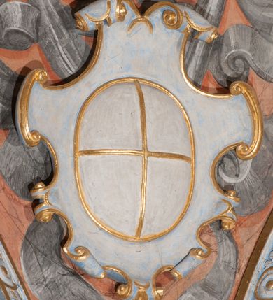 Zdjęcie nr 96: Iluzjonistyczną dekoracją malarską pokryto ściany kaplicy oraz strefę ponadcokołową: ściany tarczowe, pendentywy wokół stiukowych kartuszy herbowych oraz czaszę kopuły i wnętrze latarni. Ściany dolnej części podzielono na dwie strefy. Dolną tworzą zlokalizowane w narożach ścian iluzjonistycznie malowane pary nisz o konchach wypełnionych muszlą. W niszach ukazano osiem stojących frontalnie postaci starców, bez atrybutów i nimbów. Zapewne w ten sposób przedstawiono proroków lub apostołów. Każda z postaci ubrana jest w tunikę oraz płaszcz. Różnicuje je jedynie układ rąk, sposób kształtowania zarostu oraz kolorystyka szat. W drugiej strefie w przyłuczach arkad ukazano całopostaciowe przedstawienia uskrzydlonych aniołów trzymających narzędzia męki Pańskiej. Na ścianie wschodniej anioł prezentuje chustę Weroniki (z prawej) oraz latarnię (z lewej). Po bokach wejścia do kaplicy na ścianie północnej po prawej stronie anioł trzyma lancę i koronę cierniową, a po lewej krzyż. Z kolei na ścianie wschodniej po prawej ukazano anioła z drabiną, a po lewej z gąbką na trzcinie. Natomiast na ścianie południowej, po obu stronach zwieńczenia nagrobka, przedstawiono z prawej anioła z włócznią, a po lewej anioła z wiązką do biczowania. W tej strefie bezpośrednio przy łukach arkad wyobrażono leżące postacie geniuszy malowanych w technice en grisaille. Pod arkadą na ścianie wschodniej (ołtarzowej), ukazano dolną część owalnego jasno ugrowego baldachimu z lambrekinem i zielone, opadające paludamentum, rozsuwane kotarowo przez dwa uskrzydlone anioły. Dekoracja stanowi oprawę dla wiszącego tu obrazu Matki Boskiej z Dzieciątkiem w bogato rzeźbionej ramie. Z kolei na ścianie zachodniej wyobrażono monumentalną scenę Zdjęcia z krzyża. Jest to zwarta kompozycja ogniskująca się na wysokim drewnianym krzyżu, z którego ściągane jest martwe ciało Chrystusa. Z dwóch stron dłuższych ramion krzyż podtrzymują dwaj aniołowie. Ciało Jezusa opuszczane jest na białym pasie tkaniny przewiązanym pod jego ramionami. Chrystus ze zwisającą głową ma ręce ułożone wzdłuż ciała. Biodra przepasane ma białym perizonium. Jego skrzyżowane nogi są ugięte i jeszcze przybite gwoździem do krzyża. Gwóźdź wyciąga z nich obcęgami mężczyzna w niebieskiej, podwiniętej koszuli. Ciało opuszczają dwaj mężczyźni widoczni za poprzecznymi ramionami krzyża, trzymający końce taśmy. Człowiek z lewej strony w niebieskiej koszuli dodatkowo odbiera drugą białą taśmę od mężczyzny ubranego w szaroczarny strój. Osoba ta stoi na drabinie opartej o poprzeczne ramię krzyża. Drugi mężczyzna za krzyżem, w brązowej koszuli, lewą ręką trzyma koniec taśmy, a w uniesionej prawej młotek. Ciało Zbawiciela podtrzymuje lewą ręką kolejny mężczyzna stojący tyłem do widza na drugiej drabinie opartej o lewe ramię krzyża. Jest on ubrany w krótkie brązowe spodenki i bladozieloną koszulę. Pod krzyżem stoi zwarta siedmioosobowa grupa. Najprawdopodobniej z prawej strony ukazano św. Jana i Matkę Boską, na środku dwóch żołnierzy w ostro zakończonych hełmach, dwie kobiety, w tym zapewne Marię Magdalenę i starca widocznego z lewej strony kompozycji. Na ścianach tarczowych nad gzymsem wyobrażono po bokach okrągłych okien siedzących czterech ewangelistów i czterech ojców Kościoła. Na ścianie wschodniej znalazł się z prawej św. Jan z orłem, który w dziobie trzyma złoty kałamarz, a po lewej św. Mateusz rozmawiający z aniołem. Z kolei na ścianie południowej po lewej stronie przedstawiono św. Marka z lwem oraz św. Ambrożego trzymającego w prawej ręce naczynie z wylewającym się miodem. Na ścianie zachodniej z lewej znalazł się czytający św. Augustyn z sercem na dłoni, a z prawej św. Grzegorz Wielki z widoczną za nim tiarą i sową. Na ścianie północnej po lewej ukazano św. Hieronima z leżącym lwem, a po prawej stronie św. Łukasz z wołem. W pendentywach wykonano malarską dekorację w formie wijącej się wstęgi, na tle której widnieją stiukowe kartusze rollwerkowe, o owalnych kaboszonowych polach czwórdzielnych w krzyż. Po stronie wschodniej w pendentywach znajdują się dwa puste kartusze z niezachowanymi herbami. Natomiast herby zachowały się w pendentywach po stronie zachodniej. Na pendentywie północno-zachodnim: Jastrzębiec, Nowina, Gozdawa, Pobóg, a na południowo-zachodnim Gryf, Kotwicz, Kotwicz, Zabawa. W kopule wyobrażono Koronację Matki Boskiej adorowanej przez różnych świętych. Scenę koronacji Marii przez Trójcę Świętą przedstawiono w części wschodniej czaszy. Ukazana frontalnie Maria klęczy ze złożonymi rękami do modlitwy na obłokach. Ma owalną twarz okoloną jasnymi długimi włosami rozsypującymi się na jej ramiona. Na uniesionej ku górze głowie ma ubraną zsuwającą się białą chustę okrywającą włosy. Madonna ubrana jest w zasłaniający jej ramiona bladoniebieski płaszcz, opadający po bokach na obłoki. Nieznacznie wyżej z prawej strony na obłokach siedzi Bóg Ojciec. Wyobrażono go w trzech czwartych w prawo. Jest to starszy mężczyzna o siwych włosach i brodzie. W wyciągniętej prawej ręce nad głową Marii wraz z Chrystusem trzyma złotą koronę w typie zamkniętym. Z kolei w lewej podtrzymuje glob ze złotym krzyżykiem. Bóg Ojciec na głowie ma tiarę papieską. Ubrany jest w szaro-niebieską szatę oraz wzorzystą złotą kapę narzuconą na ramiona i spiętą pod szyją klamrą, z połami okrywającymi nogi. Naprzeciwko siedzi Chrystus widoczny w trzech czwartych w lewo z twarzą ukazaną w profilu. W wyciągniętej prawej ręce trzyma wraz z Bogiem Ojcem koronę, a lewą podtrzymuje złote berło. Chrystus ma jasne włosy opadające puklami na ramiona i podobną krótką brodę. Na głowie ma otwartą złotą koronę. Został przedstawiony z nagim torsem, na którym zaznaczono przebity bok. Jego postać otacza narzucony na ramiona bladoczerwony całun udrapowany w formie płaszcza. Nad koroną bliżej głowy Boga Ojca widoczna jest gołębica Ducha Świętego otoczona świetlistym otokiem. Ponad sceną koronacji wokół otworu do latarni wyobrażono wirujące złocisto-szare obłoki, na tle których widać uskrzydlone główki aniołków oraz postacie mniejszych i większych aniołków, które muzykują na różnych instrumentach, bądź też trzymają gałązki palmowe lub kwiaty albo kwiaty rozsypują. Uskrzydlone główki aniołków widoczne są także pośród obłoków, na których klęczy Madonna. Z prawej strony koronacji wyobrażono dwóch biskupów. Starszy, być może św. Wojciech, został przedstawiony w postawie półklęczącej w trzech czwartych w lewo. Prawą ręką zdaje się wskazywać na scenę koronacji, lewą zaś przyciska do piersi. Ma odkrytą głowę z widocznymi siwymi włosami i taką samą brodą. Ubrany jest w niebiesko-zielonkawą kapę ze złotym kapturem zakończonym chwostem. Na ziemi przy jego stopie widoczna jest złota infuła. Świętemu przyglądają się dwaj aniołowie widoczni z tyłu. Za nim klęczy młodszy biskup z leżącym przy nim na ziemi pastorałem i mieczem. Zapewne jest to św. Stanisław ze Szczepanowa. Święty ukazany został frontalnie z prawą ręką przyciśniętą do piersi, a z lewą nieznacznie odsuniętą w bok. Ma pociągłą twarz o krótkich jasnych włosach i podobnym zaroście. Ubrany jest w albę oraz szaro-bordową kapę o złotym kapturze. Przy jego kolanach stoi złota infuła, a za nim widoczny jest anioł z gałązką palmową. Za św. Stanisławem w rozwianych szatach klęczy św. Jadwiga Śląska, którą identyfikuje bryła kościoła widoczna przy jej stopach. Postać Jadwigi ukazano w profilu z założonymi rękami przed sobą. Na głowie ma niewielką złotą koronę, spod której widoczna jest biała chusta okrywająca włosy. Ubrana jest w bladoczerwoną suknię przepasaną w talii i narzucony na ramiona bladoszkarłatny płaszcz z gronostajowym kołnierzem i obszyciem. Za św. Jadwigą stoi inna święta z odsłoniętą lewą ręką wspartą o bok. Brak atrybutu nie pozwala na jej identyfikację. Ukazano ją w trzech czwartych w prawo z głową w profilu. Ma owalną twarz z wydatnym nosem. Na głowie ma niewielką złotą koronę, spod której widać jasną chustę okrywającą włosy. Ubrana jest w złocisto-szarą suknię z krótkimi rękawami i bladoczerwony rozwiany płaszcz. Pomiędzy obiema kobietami widać dwie postacie uskrzydlonych aniołów. Za świętymi siedzi z otwartą księgą wyobrażony frontalnie św. Jana Kanty. Jest to mężczyzna w średnim wieku z wysokim czołem, krótkimi brązowymi włosami i podobną brodą. Ubrany jest w bladofioletową togę akademicką z gronostajową peleryną. Trzymana przez niego księga ma czerwone okładki. Obok św. Jana Kantego namalowano czteroosobową grupę starszych mężczyzn. Pierwszy z nich, ujętych w trzech czwartych w prawo, zdaje się przyklękając, odbierać prawą ręką palmę męczeństwa podawaną mu przez widocznego nad nim anioła. Lewą ma ułożoną wzdłuż ciała. Ma podłużną twarz widoczną z profilu, otoczoną białymi włosami i spiczastą białą brodą. Ubrany jest w rozwianą jasnobeżową szatę przewiązaną w pasie i taki sam płaszcz narzucony na prawe ramię. Lewy rękaw tuniki jest podciągnięty, odsłaniając przedramię ręki. Na lewej nodze widoczny jest sandał. Za nim przedstawiono klęczącego w ujęciu trzech czwartych w lewo zakonnika eremitę, być może św. Pawła Pustelnika w białym habicie paulińskim. Zakonnik na wysokości bioder ma rozsunięte ręce. Jego twarz o wydatnym nosie otacza krzaczasta, długa, biała broda oraz białe włosy. W głębi za nim częściowo widać dwóch innych brodatych mężczyzn w beżowych szatach. Jeden z nich trzyma w dłoni palmę. W niewielkiej odległości za grupą mężczyzn na pierwszym planie klęczy na obłoku ukazany frontalnie św. Jacek. W rękach uniesionych na wysokości piersi trzyma wieżycową, złotą monstrancję i figurę Matki Boskiej. Dominikanin został przedstawiony z wysokim łysym czołem i wianuszkiem siwiejących włosów. Jego pociągła twarz o wyrazistym nosie i wąskich, nieznacznie zaciśniętych ustach pozbawiona jest zarostu. Ubrany jest w dominikański habit z czarnoniebieskim płaszczem. Z lewej strony sceny koronacji namalowano grupę czterech świętych. Na pierwszym planie widać klęczącego św. Stanisława Kostkę, wspartego na długim kiju z przywiązanym do niego węzełkiem. Święty został przedstawiony w profilu. Ma młodzieńczą, owalną twarz z krótkimi brązowymi włosami i rumianymi policzkami. Ubrany jest w bladobeżowy płaszcz, spod którego widać jasnoseledynową szatę. Za Stanisławem Kostką wyłania się w półpostaci św. Jan Nepomucen z drewnianym krzyżem podtrzymywanym lewą ręką. Jest to dojrzały mężczyzna o pociągłej twarzy, z brązowymi włosami i brodą. Z prawej strony św. Stanisława Kostki ukazano stojące dwie zakonnice, św. Kingę i zapewne bł. Salomeę. Kingę ukazano frontalnie w kontrapoście z głową uniesioną ku niebu w jasnobeżowym habicie klaryski wpadającym w brąz. Księżna prawą ręką przyciska do piersi bryłę soli, a w opuszczonej lewej trzyma kwiat lilii. U jej stóp widać model kościoła klasztornego w Starym Sączu. Obok stoi najprawdopodobniej bł. Salomea. Ukazano ją w mocnym kontrapoście, z dłońmi splecionymi na piersi i spojrzeniem skierowanym ku ziemi. Ubrana jest w rozwiany szaroniebieski habit i jasny welon. Wnętrze latarni wypełniają uskrzydlone głowy aniołków na tle złocisto-szarych obłoków.    







