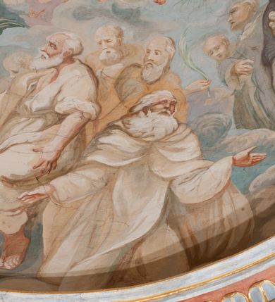 Zdjęcie nr 139: Iluzjonistyczną dekoracją malarską pokryto ściany kaplicy oraz strefę ponadcokołową: ściany tarczowe, pendentywy wokół stiukowych kartuszy herbowych oraz czaszę kopuły i wnętrze latarni. Ściany dolnej części podzielono na dwie strefy. Dolną tworzą zlokalizowane w narożach ścian iluzjonistycznie malowane pary nisz o konchach wypełnionych muszlą. W niszach ukazano osiem stojących frontalnie postaci starców, bez atrybutów i nimbów. Zapewne w ten sposób przedstawiono proroków lub apostołów. Każda z postaci ubrana jest w tunikę oraz płaszcz. Różnicuje je jedynie układ rąk, sposób kształtowania zarostu oraz kolorystyka szat. W drugiej strefie w przyłuczach arkad ukazano całopostaciowe przedstawienia uskrzydlonych aniołów trzymających narzędzia męki Pańskiej. Na ścianie wschodniej anioł prezentuje chustę Weroniki (z prawej) oraz latarnię (z lewej). Po bokach wejścia do kaplicy na ścianie północnej po prawej stronie anioł trzyma lancę i koronę cierniową, a po lewej krzyż. Z kolei na ścianie wschodniej po prawej ukazano anioła z drabiną, a po lewej z gąbką na trzcinie. Natomiast na ścianie południowej, po obu stronach zwieńczenia nagrobka, przedstawiono z prawej anioła z włócznią, a po lewej anioła z wiązką do biczowania. W tej strefie bezpośrednio przy łukach arkad wyobrażono leżące postacie geniuszy malowanych w technice en grisaille. Pod arkadą na ścianie wschodniej (ołtarzowej), ukazano dolną część owalnego jasno ugrowego baldachimu z lambrekinem i zielone, opadające paludamentum, rozsuwane kotarowo przez dwa uskrzydlone anioły. Dekoracja stanowi oprawę dla wiszącego tu obrazu Matki Boskiej z Dzieciątkiem w bogato rzeźbionej ramie. Z kolei na ścianie zachodniej wyobrażono monumentalną scenę Zdjęcia z krzyża. Jest to zwarta kompozycja ogniskująca się na wysokim drewnianym krzyżu, z którego ściągane jest martwe ciało Chrystusa. Z dwóch stron dłuższych ramion krzyż podtrzymują dwaj aniołowie. Ciało Jezusa opuszczane jest na białym pasie tkaniny przewiązanym pod jego ramionami. Chrystus ze zwisającą głową ma ręce ułożone wzdłuż ciała. Biodra przepasane ma białym perizonium. Jego skrzyżowane nogi są ugięte i jeszcze przybite gwoździem do krzyża. Gwóźdź wyciąga z nich obcęgami mężczyzna w niebieskiej, podwiniętej koszuli. Ciało opuszczają dwaj mężczyźni widoczni za poprzecznymi ramionami krzyża, trzymający końce taśmy. Człowiek z lewej strony w niebieskiej koszuli dodatkowo odbiera drugą białą taśmę od mężczyzny ubranego w szaroczarny strój. Osoba ta stoi na drabinie opartej o poprzeczne ramię krzyża. Drugi mężczyzna za krzyżem, w brązowej koszuli, lewą ręką trzyma koniec taśmy, a w uniesionej prawej młotek. Ciało Zbawiciela podtrzymuje lewą ręką kolejny mężczyzna stojący tyłem do widza na drugiej drabinie opartej o lewe ramię krzyża. Jest on ubrany w krótkie brązowe spodenki i bladozieloną koszulę. Pod krzyżem stoi zwarta siedmioosobowa grupa. Najprawdopodobniej z prawej strony ukazano św. Jana i Matkę Boską, na środku dwóch żołnierzy w ostro zakończonych hełmach, dwie kobiety, w tym zapewne Marię Magdalenę i starca widocznego z lewej strony kompozycji. Na ścianach tarczowych nad gzymsem wyobrażono po bokach okrągłych okien siedzących czterech ewangelistów i czterech ojców Kościoła. Na ścianie wschodniej znalazł się z prawej św. Jan z orłem, który w dziobie trzyma złoty kałamarz, a po lewej św. Mateusz rozmawiający z aniołem. Z kolei na ścianie południowej po lewej stronie przedstawiono św. Marka z lwem oraz św. Ambrożego trzymającego w prawej ręce naczynie z wylewającym się miodem. Na ścianie zachodniej z lewej znalazł się czytający św. Augustyn z sercem na dłoni, a z prawej św. Grzegorz Wielki z widoczną za nim tiarą i sową. Na ścianie północnej po lewej ukazano św. Hieronima z leżącym lwem, a po prawej stronie św. Łukasz z wołem. W pendentywach wykonano malarską dekorację w formie wijącej się wstęgi, na tle której widnieją stiukowe kartusze rollwerkowe, o owalnych kaboszonowych polach czwórdzielnych w krzyż. Po stronie wschodniej w pendentywach znajdują się dwa puste kartusze z niezachowanymi herbami. Natomiast herby zachowały się w pendentywach po stronie zachodniej. Na pendentywie północno-zachodnim: Jastrzębiec, Nowina, Gozdawa, Pobóg, a na południowo-zachodnim Gryf, Kotwicz, Kotwicz, Zabawa. W kopule wyobrażono Koronację Matki Boskiej adorowanej przez różnych świętych. Scenę koronacji Marii przez Trójcę Świętą przedstawiono w części wschodniej czaszy. Ukazana frontalnie Maria klęczy ze złożonymi rękami do modlitwy na obłokach. Ma owalną twarz okoloną jasnymi długimi włosami rozsypującymi się na jej ramiona. Na uniesionej ku górze głowie ma ubraną zsuwającą się białą chustę okrywającą włosy. Madonna ubrana jest w zasłaniający jej ramiona bladoniebieski płaszcz, opadający po bokach na obłoki. Nieznacznie wyżej z prawej strony na obłokach siedzi Bóg Ojciec. Wyobrażono go w trzech czwartych w prawo. Jest to starszy mężczyzna o siwych włosach i brodzie. W wyciągniętej prawej ręce nad głową Marii wraz z Chrystusem trzyma złotą koronę w typie zamkniętym. Z kolei w lewej podtrzymuje glob ze złotym krzyżykiem. Bóg Ojciec na głowie ma tiarę papieską. Ubrany jest w szaro-niebieską szatę oraz wzorzystą złotą kapę narzuconą na ramiona i spiętą pod szyją klamrą, z połami okrywającymi nogi. Naprzeciwko siedzi Chrystus widoczny w trzech czwartych w lewo z twarzą ukazaną w profilu. W wyciągniętej prawej ręce trzyma wraz z Bogiem Ojcem koronę, a lewą podtrzymuje złote berło. Chrystus ma jasne włosy opadające puklami na ramiona i podobną krótką brodę. Na głowie ma otwartą złotą koronę. Został przedstawiony z nagim torsem, na którym zaznaczono przebity bok. Jego postać otacza narzucony na ramiona bladoczerwony całun udrapowany w formie płaszcza. Nad koroną bliżej głowy Boga Ojca widoczna jest gołębica Ducha Świętego otoczona świetlistym otokiem. Ponad sceną koronacji wokół otworu do latarni wyobrażono wirujące złocisto-szare obłoki, na tle których widać uskrzydlone główki aniołków oraz postacie mniejszych i większych aniołków, które muzykują na różnych instrumentach, bądź też trzymają gałązki palmowe lub kwiaty albo kwiaty rozsypują. Uskrzydlone główki aniołków widoczne są także pośród obłoków, na których klęczy Madonna. Z prawej strony koronacji wyobrażono dwóch biskupów. Starszy, być może św. Wojciech, został przedstawiony w postawie półklęczącej w trzech czwartych w lewo. Prawą ręką zdaje się wskazywać na scenę koronacji, lewą zaś przyciska do piersi. Ma odkrytą głowę z widocznymi siwymi włosami i taką samą brodą. Ubrany jest w niebiesko-zielonkawą kapę ze złotym kapturem zakończonym chwostem. Na ziemi przy jego stopie widoczna jest złota infuła. Świętemu przyglądają się dwaj aniołowie widoczni z tyłu. Za nim klęczy młodszy biskup z leżącym przy nim na ziemi pastorałem i mieczem. Zapewne jest to św. Stanisław ze Szczepanowa. Święty ukazany został frontalnie z prawą ręką przyciśniętą do piersi, a z lewą nieznacznie odsuniętą w bok. Ma pociągłą twarz o krótkich jasnych włosach i podobnym zaroście. Ubrany jest w albę oraz szaro-bordową kapę o złotym kapturze. Przy jego kolanach stoi złota infuła, a za nim widoczny jest anioł z gałązką palmową. Za św. Stanisławem w rozwianych szatach klęczy św. Jadwiga Śląska, którą identyfikuje bryła kościoła widoczna przy jej stopach. Postać Jadwigi ukazano w profilu z założonymi rękami przed sobą. Na głowie ma niewielką złotą koronę, spod której widoczna jest biała chusta okrywająca włosy. Ubrana jest w bladoczerwoną suknię przepasaną w talii i narzucony na ramiona bladoszkarłatny płaszcz z gronostajowym kołnierzem i obszyciem. Za św. Jadwigą stoi inna święta z odsłoniętą lewą ręką wspartą o bok. Brak atrybutu nie pozwala na jej identyfikację. Ukazano ją w trzech czwartych w prawo z głową w profilu. Ma owalną twarz z wydatnym nosem. Na głowie ma niewielką złotą koronę, spod której widać jasną chustę okrywającą włosy. Ubrana jest w złocisto-szarą suknię z krótkimi rękawami i bladoczerwony rozwiany płaszcz. Pomiędzy obiema kobietami widać dwie postacie uskrzydlonych aniołów. Za świętymi siedzi z otwartą księgą wyobrażony frontalnie św. Jana Kanty. Jest to mężczyzna w średnim wieku z wysokim czołem, krótkimi brązowymi włosami i podobną brodą. Ubrany jest w bladofioletową togę akademicką z gronostajową peleryną. Trzymana przez niego księga ma czerwone okładki. Obok św. Jana Kantego namalowano czteroosobową grupę starszych mężczyzn. Pierwszy z nich, ujętych w trzech czwartych w prawo, zdaje się przyklękając, odbierać prawą ręką palmę męczeństwa podawaną mu przez widocznego nad nim anioła. Lewą ma ułożoną wzdłuż ciała. Ma podłużną twarz widoczną z profilu, otoczoną białymi włosami i spiczastą białą brodą. Ubrany jest w rozwianą jasnobeżową szatę przewiązaną w pasie i taki sam płaszcz narzucony na prawe ramię. Lewy rękaw tuniki jest podciągnięty, odsłaniając przedramię ręki. Na lewej nodze widoczny jest sandał. Za nim przedstawiono klęczącego w ujęciu trzech czwartych w lewo zakonnika eremitę, być może św. Pawła Pustelnika w białym habicie paulińskim. Zakonnik na wysokości bioder ma rozsunięte ręce. Jego twarz o wydatnym nosie otacza krzaczasta, długa, biała broda oraz białe włosy. W głębi za nim częściowo widać dwóch innych brodatych mężczyzn w beżowych szatach. Jeden z nich trzyma w dłoni palmę. W niewielkiej odległości za grupą mężczyzn na pierwszym planie klęczy na obłoku ukazany frontalnie św. Jacek. W rękach uniesionych na wysokości piersi trzyma wieżycową, złotą monstrancję i figurę Matki Boskiej. Dominikanin został przedstawiony z wysokim łysym czołem i wianuszkiem siwiejących włosów. Jego pociągła twarz o wyrazistym nosie i wąskich, nieznacznie zaciśniętych ustach pozbawiona jest zarostu. Ubrany jest w dominikański habit z czarnoniebieskim płaszczem. Z lewej strony sceny koronacji namalowano grupę czterech świętych. Na pierwszym planie widać klęczącego św. Stanisława Kostkę, wspartego na długim kiju z przywiązanym do niego węzełkiem. Święty został przedstawiony w profilu. Ma młodzieńczą, owalną twarz z krótkimi brązowymi włosami i rumianymi policzkami. Ubrany jest w bladobeżowy płaszcz, spod którego widać jasnoseledynową szatę. Za Stanisławem Kostką wyłania się w półpostaci św. Jan Nepomucen z drewnianym krzyżem podtrzymywanym lewą ręką. Jest to dojrzały mężczyzna o pociągłej twarzy, z brązowymi włosami i brodą. Z prawej strony św. Stanisława Kostki ukazano stojące dwie zakonnice, św. Kingę i zapewne bł. Salomeę. Kingę ukazano frontalnie w kontrapoście z głową uniesioną ku niebu w jasnobeżowym habicie klaryski wpadającym w brąz. Księżna prawą ręką przyciska do piersi bryłę soli, a w opuszczonej lewej trzyma kwiat lilii. U jej stóp widać model kościoła klasztornego w Starym Sączu. Obok stoi najprawdopodobniej bł. Salomea. Ukazano ją w mocnym kontrapoście, z dłońmi splecionymi na piersi i spojrzeniem skierowanym ku ziemi. Ubrana jest w rozwiany szaroniebieski habit i jasny welon. Wnętrze latarni wypełniają uskrzydlone głowy aniołków na tle złocisto-szarych obłoków.    







