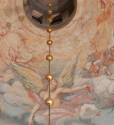 Zdjęcie nr 168: Iluzjonistyczną dekoracją malarską pokryto ściany kaplicy oraz strefę ponadcokołową: ściany tarczowe, pendentywy wokół stiukowych kartuszy herbowych oraz czaszę kopuły i wnętrze latarni. Ściany dolnej części podzielono na dwie strefy. Dolną tworzą zlokalizowane w narożach ścian iluzjonistycznie malowane pary nisz o konchach wypełnionych muszlą. W niszach ukazano osiem stojących frontalnie postaci starców, bez atrybutów i nimbów. Zapewne w ten sposób przedstawiono proroków lub apostołów. Każda z postaci ubrana jest w tunikę oraz płaszcz. Różnicuje je jedynie układ rąk, sposób kształtowania zarostu oraz kolorystyka szat. W drugiej strefie w przyłuczach arkad ukazano całopostaciowe przedstawienia uskrzydlonych aniołów trzymających narzędzia męki Pańskiej. Na ścianie wschodniej anioł prezentuje chustę Weroniki (z prawej) oraz latarnię (z lewej). Po bokach wejścia do kaplicy na ścianie północnej po prawej stronie anioł trzyma lancę i koronę cierniową, a po lewej krzyż. Z kolei na ścianie wschodniej po prawej ukazano anioła z drabiną, a po lewej z gąbką na trzcinie. Natomiast na ścianie południowej, po obu stronach zwieńczenia nagrobka, przedstawiono z prawej anioła z włócznią, a po lewej anioła z wiązką do biczowania. W tej strefie bezpośrednio przy łukach arkad wyobrażono leżące postacie geniuszy malowanych w technice en grisaille. Pod arkadą na ścianie wschodniej (ołtarzowej), ukazano dolną część owalnego jasno ugrowego baldachimu z lambrekinem i zielone, opadające paludamentum, rozsuwane kotarowo przez dwa uskrzydlone anioły. Dekoracja stanowi oprawę dla wiszącego tu obrazu Matki Boskiej z Dzieciątkiem w bogato rzeźbionej ramie. Z kolei na ścianie zachodniej wyobrażono monumentalną scenę Zdjęcia z krzyża. Jest to zwarta kompozycja ogniskująca się na wysokim drewnianym krzyżu, z którego ściągane jest martwe ciało Chrystusa. Z dwóch stron dłuższych ramion krzyż podtrzymują dwaj aniołowie. Ciało Jezusa opuszczane jest na białym pasie tkaniny przewiązanym pod jego ramionami. Chrystus ze zwisającą głową ma ręce ułożone wzdłuż ciała. Biodra przepasane ma białym perizonium. Jego skrzyżowane nogi są ugięte i jeszcze przybite gwoździem do krzyża. Gwóźdź wyciąga z nich obcęgami mężczyzna w niebieskiej, podwiniętej koszuli. Ciało opuszczają dwaj mężczyźni widoczni za poprzecznymi ramionami krzyża, trzymający końce taśmy. Człowiek z lewej strony w niebieskiej koszuli dodatkowo odbiera drugą białą taśmę od mężczyzny ubranego w szaroczarny strój. Osoba ta stoi na drabinie opartej o poprzeczne ramię krzyża. Drugi mężczyzna za krzyżem, w brązowej koszuli, lewą ręką trzyma koniec taśmy, a w uniesionej prawej młotek. Ciało Zbawiciela podtrzymuje lewą ręką kolejny mężczyzna stojący tyłem do widza na drugiej drabinie opartej o lewe ramię krzyża. Jest on ubrany w krótkie brązowe spodenki i bladozieloną koszulę. Pod krzyżem stoi zwarta siedmioosobowa grupa. Najprawdopodobniej z prawej strony ukazano św. Jana i Matkę Boską, na środku dwóch żołnierzy w ostro zakończonych hełmach, dwie kobiety, w tym zapewne Marię Magdalenę i starca widocznego z lewej strony kompozycji. Na ścianach tarczowych nad gzymsem wyobrażono po bokach okrągłych okien siedzących czterech ewangelistów i czterech ojców Kościoła. Na ścianie wschodniej znalazł się z prawej św. Jan z orłem, który w dziobie trzyma złoty kałamarz, a po lewej św. Mateusz rozmawiający z aniołem. Z kolei na ścianie południowej po lewej stronie przedstawiono św. Marka z lwem oraz św. Ambrożego trzymającego w prawej ręce naczynie z wylewającym się miodem. Na ścianie zachodniej z lewej znalazł się czytający św. Augustyn z sercem na dłoni, a z prawej św. Grzegorz Wielki z widoczną za nim tiarą i sową. Na ścianie północnej po lewej ukazano św. Hieronima z leżącym lwem, a po prawej stronie św. Łukasz z wołem. W pendentywach wykonano malarską dekorację w formie wijącej się wstęgi, na tle której widnieją stiukowe kartusze rollwerkowe, o owalnych kaboszonowych polach czwórdzielnych w krzyż. Po stronie wschodniej w pendentywach znajdują się dwa puste kartusze z niezachowanymi herbami. Natomiast herby zachowały się w pendentywach po stronie zachodniej. Na pendentywie północno-zachodnim: Jastrzębiec, Nowina, Gozdawa, Pobóg, a na południowo-zachodnim Gryf, Kotwicz, Kotwicz, Zabawa. W kopule wyobrażono Koronację Matki Boskiej adorowanej przez różnych świętych. Scenę koronacji Marii przez Trójcę Świętą przedstawiono w części wschodniej czaszy. Ukazana frontalnie Maria klęczy ze złożonymi rękami do modlitwy na obłokach. Ma owalną twarz okoloną jasnymi długimi włosami rozsypującymi się na jej ramiona. Na uniesionej ku górze głowie ma ubraną zsuwającą się białą chustę okrywającą włosy. Madonna ubrana jest w zasłaniający jej ramiona bladoniebieski płaszcz, opadający po bokach na obłoki. Nieznacznie wyżej z prawej strony na obłokach siedzi Bóg Ojciec. Wyobrażono go w trzech czwartych w prawo. Jest to starszy mężczyzna o siwych włosach i brodzie. W wyciągniętej prawej ręce nad głową Marii wraz z Chrystusem trzyma złotą koronę w typie zamkniętym. Z kolei w lewej podtrzymuje glob ze złotym krzyżykiem. Bóg Ojciec na głowie ma tiarę papieską. Ubrany jest w szaro-niebieską szatę oraz wzorzystą złotą kapę narzuconą na ramiona i spiętą pod szyją klamrą, z połami okrywającymi nogi. Naprzeciwko siedzi Chrystus widoczny w trzech czwartych w lewo z twarzą ukazaną w profilu. W wyciągniętej prawej ręce trzyma wraz z Bogiem Ojcem koronę, a lewą podtrzymuje złote berło. Chrystus ma jasne włosy opadające puklami na ramiona i podobną krótką brodę. Na głowie ma otwartą złotą koronę. Został przedstawiony z nagim torsem, na którym zaznaczono przebity bok. Jego postać otacza narzucony na ramiona bladoczerwony całun udrapowany w formie płaszcza. Nad koroną bliżej głowy Boga Ojca widoczna jest gołębica Ducha Świętego otoczona świetlistym otokiem. Ponad sceną koronacji wokół otworu do latarni wyobrażono wirujące złocisto-szare obłoki, na tle których widać uskrzydlone główki aniołków oraz postacie mniejszych i większych aniołków, które muzykują na różnych instrumentach, bądź też trzymają gałązki palmowe lub kwiaty albo kwiaty rozsypują. Uskrzydlone główki aniołków widoczne są także pośród obłoków, na których klęczy Madonna. Z prawej strony koronacji wyobrażono dwóch biskupów. Starszy, być może św. Wojciech, został przedstawiony w postawie półklęczącej w trzech czwartych w lewo. Prawą ręką zdaje się wskazywać na scenę koronacji, lewą zaś przyciska do piersi. Ma odkrytą głowę z widocznymi siwymi włosami i taką samą brodą. Ubrany jest w niebiesko-zielonkawą kapę ze złotym kapturem zakończonym chwostem. Na ziemi przy jego stopie widoczna jest złota infuła. Świętemu przyglądają się dwaj aniołowie widoczni z tyłu. Za nim klęczy młodszy biskup z leżącym przy nim na ziemi pastorałem i mieczem. Zapewne jest to św. Stanisław ze Szczepanowa. Święty ukazany został frontalnie z prawą ręką przyciśniętą do piersi, a z lewą nieznacznie odsuniętą w bok. Ma pociągłą twarz o krótkich jasnych włosach i podobnym zaroście. Ubrany jest w albę oraz szaro-bordową kapę o złotym kapturze. Przy jego kolanach stoi złota infuła, a za nim widoczny jest anioł z gałązką palmową. Za św. Stanisławem w rozwianych szatach klęczy św. Jadwiga Śląska, którą identyfikuje bryła kościoła widoczna przy jej stopach. Postać Jadwigi ukazano w profilu z założonymi rękami przed sobą. Na głowie ma niewielką złotą koronę, spod której widoczna jest biała chusta okrywająca włosy. Ubrana jest w bladoczerwoną suknię przepasaną w talii i narzucony na ramiona bladoszkarłatny płaszcz z gronostajowym kołnierzem i obszyciem. Za św. Jadwigą stoi inna święta z odsłoniętą lewą ręką wspartą o bok. Brak atrybutu nie pozwala na jej identyfikację. Ukazano ją w trzech czwartych w prawo z głową w profilu. Ma owalną twarz z wydatnym nosem. Na głowie ma niewielką złotą koronę, spod której widać jasną chustę okrywającą włosy. Ubrana jest w złocisto-szarą suknię z krótkimi rękawami i bladoczerwony rozwiany płaszcz. Pomiędzy obiema kobietami widać dwie postacie uskrzydlonych aniołów. Za świętymi siedzi z otwartą księgą wyobrażony frontalnie św. Jana Kanty. Jest to mężczyzna w średnim wieku z wysokim czołem, krótkimi brązowymi włosami i podobną brodą. Ubrany jest w bladofioletową togę akademicką z gronostajową peleryną. Trzymana przez niego księga ma czerwone okładki. Obok św. Jana Kantego namalowano czteroosobową grupę starszych mężczyzn. Pierwszy z nich, ujętych w trzech czwartych w prawo, zdaje się przyklękając, odbierać prawą ręką palmę męczeństwa podawaną mu przez widocznego nad nim anioła. Lewą ma ułożoną wzdłuż ciała. Ma podłużną twarz widoczną z profilu, otoczoną białymi włosami i spiczastą białą brodą. Ubrany jest w rozwianą jasnobeżową szatę przewiązaną w pasie i taki sam płaszcz narzucony na prawe ramię. Lewy rękaw tuniki jest podciągnięty, odsłaniając przedramię ręki. Na lewej nodze widoczny jest sandał. Za nim przedstawiono klęczącego w ujęciu trzech czwartych w lewo zakonnika eremitę, być może św. Pawła Pustelnika w białym habicie paulińskim. Zakonnik na wysokości bioder ma rozsunięte ręce. Jego twarz o wydatnym nosie otacza krzaczasta, długa, biała broda oraz białe włosy. W głębi za nim częściowo widać dwóch innych brodatych mężczyzn w beżowych szatach. Jeden z nich trzyma w dłoni palmę. W niewielkiej odległości za grupą mężczyzn na pierwszym planie klęczy na obłoku ukazany frontalnie św. Jacek. W rękach uniesionych na wysokości piersi trzyma wieżycową, złotą monstrancję i figurę Matki Boskiej. Dominikanin został przedstawiony z wysokim łysym czołem i wianuszkiem siwiejących włosów. Jego pociągła twarz o wyrazistym nosie i wąskich, nieznacznie zaciśniętych ustach pozbawiona jest zarostu. Ubrany jest w dominikański habit z czarnoniebieskim płaszczem. Z lewej strony sceny koronacji namalowano grupę czterech świętych. Na pierwszym planie widać klęczącego św. Stanisława Kostkę, wspartego na długim kiju z przywiązanym do niego węzełkiem. Święty został przedstawiony w profilu. Ma młodzieńczą, owalną twarz z krótkimi brązowymi włosami i rumianymi policzkami. Ubrany jest w bladobeżowy płaszcz, spod którego widać jasnoseledynową szatę. Za Stanisławem Kostką wyłania się w półpostaci św. Jan Nepomucen z drewnianym krzyżem podtrzymywanym lewą ręką. Jest to dojrzały mężczyzna o pociągłej twarzy, z brązowymi włosami i brodą. Z prawej strony św. Stanisława Kostki ukazano stojące dwie zakonnice, św. Kingę i zapewne bł. Salomeę. Kingę ukazano frontalnie w kontrapoście z głową uniesioną ku niebu w jasnobeżowym habicie klaryski wpadającym w brąz. Księżna prawą ręką przyciska do piersi bryłę soli, a w opuszczonej lewej trzyma kwiat lilii. U jej stóp widać model kościoła klasztornego w Starym Sączu. Obok stoi najprawdopodobniej bł. Salomea. Ukazano ją w mocnym kontrapoście, z dłońmi splecionymi na piersi i spojrzeniem skierowanym ku ziemi. Ubrana jest w rozwiany szaroniebieski habit i jasny welon. Wnętrze latarni wypełniają uskrzydlone głowy aniołków na tle złocisto-szarych obłoków.    







