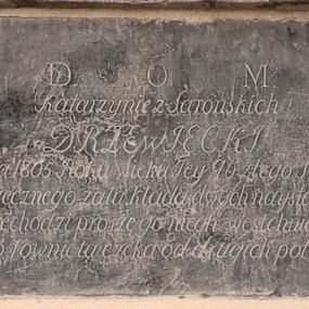 Zdjęcie nr 1: Płyta o formie leżącego prostokąta. W polu inskrypcja
„D(eo) O(ptimo) M(aximo) / Katarzynie z Sarońskich / DRZEWIECKI / dnia 2 Grudnia 1805 Roku wieku Iey 96 z tego Światu zeszła / Świadectwo wiecznego żalu kładą dwoch naystarszych Wnuko / kto przechodzi proszę go niech westchnie do Nieba / Bo go rownie ta czeka od drugich potrzeba”.