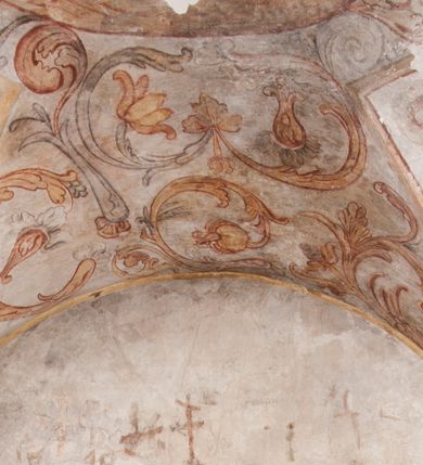 Zdjęcie nr 1: Polichromia pokrywa ściany i sklepienie kolebkowe z lunetami czworobocznej, dwuprzęsłowej zakrystii. Pole sklepienia wypełnia dekoracja ornamentalna utworzona ze zawijanych liści akantu, stylizowanych kwiatów oraz wazonów z kwiatami. Pośrodku sklepienia umieszczono w owalu w kartuszu fragmentarycznie zachowaną scenę Koronacji Marii. W centrum kompozycji zachowała się głowa Marii ujęta w trzy czwarte w prawo z widocznym fragmentem prawego ramienia i ułożonej do modlitwy prawej ręki. Po prawej stronie widać postać tronującego Boga Ojca w złotej koronie, z brodą, trzymającego złotą koronę nad głową Marii. Z lewej można dostrzec fragment ręki Chrystusa oraz fragment jego czerwonej szaty i lewej stopy. Na ścianie wschodniej dekorację malarską w postaci wici utworzonej ze stylizowanych liści akantu i kwiatów poprowadzono w glifie okiennym. Wokół okna utworzono malowane obramienie z motywami stylizowanego ornamentu rollwerkowego. Ponad oknem w glifie znajduje się malowany chrystogram "IHS". Po prawej stronie okna widoczne jest całopostaciowe przedstawienie proroka Eliasza z rozłożonymi rękami. Postać została ujęta w trzech czwartych w prawo. Ma pociągłą twarz okoloną zarostem z wydatnym nosem i ustami. Ubrana jest w strój wschodni - długą szatę z bladoczerwonym płaszczem z kołnierzykiem spiętym przy szyi oraz z rozciętymi rękawami. Na głowie ma szaroniebieski turban. Ponad nim widać lecącego kruka. Obok mężczyzny z prawej strony widoczna jest niewielka sekwencja krajobrazowa z motywem drzewa. Eliasz zwrócony jest w stronę sceny z Ostatnią Wieczerzą wykonaną w pierwszym przęśle ściany południowej zakrystii. Ostatnią Wieczerzę z prawej strony zamyka malowana kolumna z kapitelem rozdzielająca ścianę na dwa przęsła. Na tle altany ze schodami po lewej, flankowanej trzema kolumnami na wysokich cokołach, ukazano Chrystusa i dwunastu apostołów siedzący przy okrągłym, okazałym stole. Ponad stołem wisi płonącą lampa. Stół nakryto białym obrusem zastawionym siedmioma talerzami, owalną misą pośrodku, trzema okrągłymi bochenkami chleba, dwoma nożami i kielichem. Siedzący centralnie za stołem Chrystus został ukazany frontalnie. Zbawiciel ma zmęczoną twarz otoczoną brodą i długimi włosami, spływającymi na ramiona. Ubrany jest w białą tunikę i niebieski płaszcz przerzucony przez lewe ramię. O jego pierś opiera się zamyślony św. Jan, wspierający głowę na prawej ręce trzymanej na stole. Lewą rękę położoną na blacie ma zgiętą w łokciu. Wokół stołu siedzą rozmawiający ze sobą pozostali apostołowie. Są to starsi, brodaci mężczyźni, niektórzy z nich są łysi. Ubrani są w tuniki i narzucone na ramionach płaszcze. Można spośród nich wyróżnić siedzącego po prawe strony Chrystusa św. Piotra oraz Judasza widocznego jako pierwszego po lewej stronie kompozycji. Judasza ukazanego frontalnie identyfikuje żółta szata oraz trzymany w prawej ręce mieszek ze srebnikami. Powyżej w podłuczu lunety namalowano siedzącego, starszego brodatego mężczyznę ujętego w trzech czwartych w prawo. Jest to ewangelista widoczny do kolan. Prawą rękę przyciska do piersi lewą zaś opiera o stół ustawiony z prawej strony kompozycji z ułożoną na nim księgą. Jego twarz charakteryzuje wydatny nos i usta oraz spojrzenie skierowane na widza. W drugim przęśle ściany  
południowej dekoracje tworzy stylizowana wić akantowo-kwiatowa w glifie okiennym oraz otaczające okno obramienie utworzone z motywów rollwerkowych. Nie zachowała się polichromia w lunecie powyżej okna. Na zachodniej ścianie w glifie dawnego otworu wejściowego obramionego żółtą listwą, wykonano dekorację malarską składającą się z malowanych romboidalnych płycin pokrytych czerwonawą marmoryzacją. Ponad glifem na ścianie znajduje się czerwony krzyż równoramienny rozdzielający datę 16 / 46. Na ścianie z prawej strony otworu wyobrażono Ukrzyżowanie Chrystusa na polu pokrytym licznymi, stojącymi krzyżami. Postać Zbawiciela zachowała się fragmentarycznie w partii tułowia i nóg. Powyżej pole w lunecie ozdobiono stylizowaną wicią akantowo-kwiatową. Ścianę północną w pierwszym przęśle wypełnionym szafą zakrystyjną udekorowano rozpostartym, czerwonym paludamentum z baldachimem. Powyżej w lunecie zachowało się bardzo zniszczone przedstawienie św. Jana Ewangelisty, którego można rozpoznać po młodzieńczej, pociągłej twarz o wydatnych rysach. Z postaci zachowały się jeszcze  fragmenty stóp widoczne nad baldachimem. W drugim prześle w dolnej strefie przepruto drzwi z otworem zamkniętym łukiem odcinkowym, obramienionym złocistą taśmą. W nadprożu znalazła się stylizowana wić akantowo-kwiatowa. Powyżej, w górnej strefie namalowano modlitwę Chrystusa w Ogrójcu. Na pierwszym planie kompozycji widoczny jest klęczący na ziemi Zbawiciel ujęty w trzech czwartych w prawo. Lewą rękę ma przyłożoną do piersi, drugą zaś odsuniętą od tułowia. Jego uniesioną głowę ku górze otacza ciemna broda i długie włosy spływające na plecy. Chrystus ma wydatny nos i usta. Ubrany jest w obszerną, jasnooliwkową tunikę przewiązaną w pasie oraz niebieskoszary płaszcz przerzucony przez lewe ramię i rękę. Jezus wpatruje się w zjawiającego mu się powyżej uskrzydlonego anioła ukazanego w dwóch trzecich na obłokach. Anioł w wyciągniętej prawej ręce trzyma złoty kielich, a prawą podtrzymuje opary o ramię krzyż. Ubrany jest w baldoczerwoną tunikę przewiązaną w pasie. Z prawej strony Jezusa widocznych jest trzech śpiących apostołów. Na pierwszym planie ukazano leżącego św. Piotra z głową wspartą na lewej ręce. Jest to starszy mężczyzna z łysym czołem i siwiejącymi włosami i brodą. Ubrany jest w bladoniebieską tunikę i ciemnoochrowy płaszcz. Za nim widać siedzącego św. Jana z głową wspartą na ręce, którą podpiera o prawe kolano. Jest to młodzieniec o długich włosach, ubrany w blado oliwkową tunikę i baldoczerwony płaszcz. O niewielki wzgórek z lewej strony Jana oparty jest św. Jakub. Jest to starszy mężczyzna z brązową brodą i włosami ubrany w bladooliwkowy płaszcz. Za Zbawicielem z lewej strony kompozycji widać drewniany płot z bramką, przez którą do ogrodu wchodzi Judasz w jasno-chórowej szacie, prowadzący zbrojny oddział sług świątynnych. W głębi kompozycji ukazano panoramę Jerozolimy. Powyżej na sklepieniu lunety wyobrażono siedzącego ewangelistę, który ukazany został jako starzec z długą siwą brodą i łysiejącym czołem. Mężczyzna wspierając prawą rękę o stół podpiera nią głowę. Lewą ma położoną na kolanie. Ubrany jest w szarą tunikę oraz bladoczerwony płaszcz przerzucony przez prawe ramię i okrywający kolana.    
