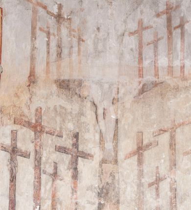 Zdjęcie nr 9: Polichromia pokrywa ściany i sklepienie kolebkowe z lunetami czworobocznej, dwuprzęsłowej zakrystii. Pole sklepienia wypełnia dekoracja ornamentalna utworzona ze zawijanych liści akantu, stylizowanych kwiatów oraz wazonów z kwiatami. Pośrodku sklepienia umieszczono w owalu w kartuszu fragmentarycznie zachowaną scenę Koronacji Marii. W centrum kompozycji zachowała się głowa Marii ujęta w trzy czwarte w prawo z widocznym fragmentem prawego ramienia i ułożonej do modlitwy prawej ręki. Po prawej stronie widać postać tronującego Boga Ojca w złotej koronie, z brodą, trzymającego złotą koronę nad głową Marii. Z lewej można dostrzec fragment ręki Chrystusa oraz fragment jego czerwonej szaty i lewej stopy. Na ścianie wschodniej dekorację malarską w postaci wici utworzonej ze stylizowanych liści akantu i kwiatów poprowadzono w glifie okiennym. Wokół okna utworzono malowane obramienie z motywami stylizowanego ornamentu rollwerkowego. Ponad oknem w glifie znajduje się malowany chrystogram &quot;IHS&quot;. Po prawej stronie okna widoczne jest całopostaciowe przedstawienie proroka Eliasza z rozłożonymi rękami. Postać została ujęta w trzech czwartych w prawo. Ma pociągłą twarz okoloną zarostem z wydatnym nosem i ustami. Ubrana jest w strój wschodni - długą szatę z bladoczerwonym płaszczem z kołnierzykiem spiętym przy szyi oraz z rozciętymi rękawami. Na głowie ma szaroniebieski turban. Ponad nim widać lecącego kruka. Obok mężczyzny z prawej strony widoczna jest niewielka sekwencja krajobrazowa z motywem drzewa. Eliasz zwrócony jest w stronę sceny z Ostatnią Wieczerzą wykonaną w pierwszym przęśle ściany południowej zakrystii. Ostatnią Wieczerzę z prawej strony zamyka malowana kolumna z kapitelem rozdzielająca ścianę na dwa przęsła. Na tle altany ze schodami po lewej, flankowanej trzema kolumnami na wysokich cokołach, ukazano Chrystusa i dwunastu apostołów siedzący przy okrągłym, okazałym stole. Ponad stołem wisi płonącą lampa. Stół nakryto białym obrusem zastawionym siedmioma talerzami, owalną misą pośrodku, trzema okrągłymi bochenkami chleba, dwoma nożami i kielichem. Siedzący centralnie za stołem Chrystus został ukazany frontalnie. Zbawiciel ma zmęczoną twarz otoczoną brodą i długimi włosami, spływającymi na ramiona. Ubrany jest w białą tunikę i niebieski płaszcz przerzucony przez lewe ramię. O jego pierś opiera się zamyślony św. Jan, wspierający głowę na prawej ręce trzymanej na stole. Lewą rękę położoną na blacie ma zgiętą w łokciu. Wokół stołu siedzą rozmawiający ze sobą pozostali apostołowie. Są to starsi, brodaci mężczyźni, niektórzy z nich są łysi. Ubrani są w tuniki i narzucone na ramionach płaszcze. Można spośród nich wyróżnić siedzącego po prawe strony Chrystusa św. Piotra oraz Judasza widocznego jako pierwszego po lewej stronie kompozycji. Judasza ukazanego frontalnie identyfikuje żółta szata oraz trzymany w prawej ręce mieszek ze srebnikami. Powyżej w podłuczu lunety namalowano siedzącego, starszego brodatego mężczyznę ujętego w trzech czwartych w prawo. Jest to ewangelista widoczny do kolan. Prawą rękę przyciska do piersi lewą zaś opiera o stół ustawiony z prawej strony kompozycji z ułożoną na nim księgą. Jego twarz charakteryzuje wydatny nos i usta oraz spojrzenie skierowane na widza. W drugim przęśle ściany  
południowej dekoracje tworzy stylizowana wić akantowo-kwiatowa w glifie okiennym oraz otaczające okno obramienie utworzone z motywów rollwerkowych. Nie zachowała się polichromia w lunecie powyżej okna. Na zachodniej ścianie w glifie dawnego otworu wejściowego obramionego żółtą listwą, wykonano dekorację malarską składającą się z malowanych romboidalnych płycin pokrytych czerwonawą marmoryzacją. Ponad glifem na ścianie znajduje się czerwony krzyż równoramienny rozdzielający datę 16 / 46. Na ścianie z prawej strony otworu wyobrażono Ukrzyżowanie Chrystusa na polu pokrytym licznymi, stojącymi krzyżami. Postać Zbawiciela zachowała się fragmentarycznie w partii tułowia i nóg. Powyżej pole w lunecie ozdobiono stylizowaną wicią akantowo-kwiatową. Ścianę północną w pierwszym przęśle wypełnionym szafą zakrystyjną udekorowano rozpostartym, czerwonym paludamentum z baldachimem. Powyżej w lunecie zachowało się bardzo zniszczone przedstawienie św. Jana Ewangelisty, którego można rozpoznać po młodzieńczej, pociągłej twarz o wydatnych rysach. Z postaci zachowały się jeszcze  fragmenty stóp widoczne nad baldachimem. W drugim prześle w dolnej strefie przepruto drzwi z otworem zamkniętym łukiem odcinkowym, obramienionym złocistą taśmą. W nadprożu znalazła się stylizowana wić akantowo-kwiatowa. Powyżej, w górnej strefie namalowano modlitwę Chrystusa w Ogrójcu. Na pierwszym planie kompozycji widoczny jest klęczący na ziemi Zbawiciel ujęty w trzech czwartych w prawo. Lewą rękę ma przyłożoną do piersi, drugą zaś odsuniętą od tułowia. Jego uniesioną głowę ku górze otacza ciemna broda i długie włosy spływające na plecy. Chrystus ma wydatny nos i usta. Ubrany jest w obszerną, jasnooliwkową tunikę przewiązaną w pasie oraz niebieskoszary płaszcz przerzucony przez lewe ramię i rękę. Jezus wpatruje się w zjawiającego mu się powyżej uskrzydlonego anioła ukazanego w dwóch trzecich na obłokach. Anioł w wyciągniętej prawej ręce trzyma złoty kielich, a prawą podtrzymuje opary o ramię krzyż. Ubrany jest w baldoczerwoną tunikę przewiązaną w pasie. Z prawej strony Jezusa widocznych jest trzech śpiących apostołów. Na pierwszym planie ukazano leżącego św. Piotra z głową wspartą na lewej ręce. Jest to starszy mężczyzna z łysym czołem i siwiejącymi włosami i brodą. Ubrany jest w bladoniebieską tunikę i ciemnoochrowy płaszcz. Za nim widać siedzącego św. Jana z głową wspartą na ręce, którą podpiera o prawe kolano. Jest to młodzieniec o długich włosach, ubrany w blado oliwkową tunikę i baldoczerwony płaszcz. O niewielki wzgórek z lewej strony Jana oparty jest św. Jakub. Jest to starszy mężczyzna z brązową brodą i włosami ubrany w bladooliwkowy płaszcz. Za Zbawicielem z lewej strony kompozycji widać drewniany płot z bramką, przez którą do ogrodu wchodzi Judasz w jasno-chórowej szacie, prowadzący zbrojny oddział sług świątynnych. W głębi kompozycji ukazano panoramę Jerozolimy. Powyżej na sklepieniu lunety wyobrażono siedzącego ewangelistę, który ukazany został jako starzec z długą siwą brodą i łysiejącym czołem. Mężczyzna wspierając prawą rękę o stół podpiera nią głowę. Lewą ma położoną na kolanie. Ubrany jest w szarą tunikę oraz bladoczerwony płaszcz przerzucony przez prawe ramię i okrywający kolana.    
