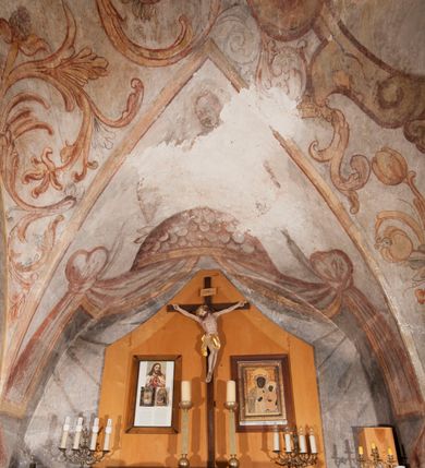 Zdjęcie nr 2: Polichromia pokrywa ściany i sklepienie kolebkowe z lunetami czworobocznej, dwuprzęsłowej zakrystii. Pole sklepienia wypełnia dekoracja ornamentalna utworzona ze zawijanych liści akantu, stylizowanych kwiatów oraz wazonów z kwiatami. Pośrodku sklepienia umieszczono w owalu w kartuszu fragmentarycznie zachowaną scenę Koronacji Marii. W centrum kompozycji zachowała się głowa Marii ujęta w trzy czwarte w prawo z widocznym fragmentem prawego ramienia i ułożonej do modlitwy prawej ręki. Po prawej stronie widać postać tronującego Boga Ojca w złotej koronie, z brodą, trzymającego złotą koronę nad głową Marii. Z lewej można dostrzec fragment ręki Chrystusa oraz fragment jego czerwonej szaty i lewej stopy. Na ścianie wschodniej dekorację malarską w postaci wici utworzonej ze stylizowanych liści akantu i kwiatów poprowadzono w glifie okiennym. Wokół okna utworzono malowane obramienie z motywami stylizowanego ornamentu rollwerkowego. Ponad oknem w glifie znajduje się malowany chrystogram &quot;IHS&quot;. Po prawej stronie okna widoczne jest całopostaciowe przedstawienie proroka Eliasza z rozłożonymi rękami. Postać została ujęta w trzech czwartych w prawo. Ma pociągłą twarz okoloną zarostem z wydatnym nosem i ustami. Ubrana jest w strój wschodni - długą szatę z bladoczerwonym płaszczem z kołnierzykiem spiętym przy szyi oraz z rozciętymi rękawami. Na głowie ma szaroniebieski turban. Ponad nim widać lecącego kruka. Obok mężczyzny z prawej strony widoczna jest niewielka sekwencja krajobrazowa z motywem drzewa. Eliasz zwrócony jest w stronę sceny z Ostatnią Wieczerzą wykonaną w pierwszym przęśle ściany południowej zakrystii. Ostatnią Wieczerzę z prawej strony zamyka malowana kolumna z kapitelem rozdzielająca ścianę na dwa przęsła. Na tle altany ze schodami po lewej, flankowanej trzema kolumnami na wysokich cokołach, ukazano Chrystusa i dwunastu apostołów siedzący przy okrągłym, okazałym stole. Ponad stołem wisi płonącą lampa. Stół nakryto białym obrusem zastawionym siedmioma talerzami, owalną misą pośrodku, trzema okrągłymi bochenkami chleba, dwoma nożami i kielichem. Siedzący centralnie za stołem Chrystus został ukazany frontalnie. Zbawiciel ma zmęczoną twarz otoczoną brodą i długimi włosami, spływającymi na ramiona. Ubrany jest w białą tunikę i niebieski płaszcz przerzucony przez lewe ramię. O jego pierś opiera się zamyślony św. Jan, wspierający głowę na prawej ręce trzymanej na stole. Lewą rękę położoną na blacie ma zgiętą w łokciu. Wokół stołu siedzą rozmawiający ze sobą pozostali apostołowie. Są to starsi, brodaci mężczyźni, niektórzy z nich są łysi. Ubrani są w tuniki i narzucone na ramionach płaszcze. Można spośród nich wyróżnić siedzącego po prawe strony Chrystusa św. Piotra oraz Judasza widocznego jako pierwszego po lewej stronie kompozycji. Judasza ukazanego frontalnie identyfikuje żółta szata oraz trzymany w prawej ręce mieszek ze srebnikami. Powyżej w podłuczu lunety namalowano siedzącego, starszego brodatego mężczyznę ujętego w trzech czwartych w prawo. Jest to ewangelista widoczny do kolan. Prawą rękę przyciska do piersi lewą zaś opiera o stół ustawiony z prawej strony kompozycji z ułożoną na nim księgą. Jego twarz charakteryzuje wydatny nos i usta oraz spojrzenie skierowane na widza. W drugim przęśle ściany  
południowej dekoracje tworzy stylizowana wić akantowo-kwiatowa w glifie okiennym oraz otaczające okno obramienie utworzone z motywów rollwerkowych. Nie zachowała się polichromia w lunecie powyżej okna. Na zachodniej ścianie w glifie dawnego otworu wejściowego obramionego żółtą listwą, wykonano dekorację malarską składającą się z malowanych romboidalnych płycin pokrytych czerwonawą marmoryzacją. Ponad glifem na ścianie znajduje się czerwony krzyż równoramienny rozdzielający datę 16 / 46. Na ścianie z prawej strony otworu wyobrażono Ukrzyżowanie Chrystusa na polu pokrytym licznymi, stojącymi krzyżami. Postać Zbawiciela zachowała się fragmentarycznie w partii tułowia i nóg. Powyżej pole w lunecie ozdobiono stylizowaną wicią akantowo-kwiatową. Ścianę północną w pierwszym przęśle wypełnionym szafą zakrystyjną udekorowano rozpostartym, czerwonym paludamentum z baldachimem. Powyżej w lunecie zachowało się bardzo zniszczone przedstawienie św. Jana Ewangelisty, którego można rozpoznać po młodzieńczej, pociągłej twarz o wydatnych rysach. Z postaci zachowały się jeszcze  fragmenty stóp widoczne nad baldachimem. W drugim prześle w dolnej strefie przepruto drzwi z otworem zamkniętym łukiem odcinkowym, obramienionym złocistą taśmą. W nadprożu znalazła się stylizowana wić akantowo-kwiatowa. Powyżej, w górnej strefie namalowano modlitwę Chrystusa w Ogrójcu. Na pierwszym planie kompozycji widoczny jest klęczący na ziemi Zbawiciel ujęty w trzech czwartych w prawo. Lewą rękę ma przyłożoną do piersi, drugą zaś odsuniętą od tułowia. Jego uniesioną głowę ku górze otacza ciemna broda i długie włosy spływające na plecy. Chrystus ma wydatny nos i usta. Ubrany jest w obszerną, jasnooliwkową tunikę przewiązaną w pasie oraz niebieskoszary płaszcz przerzucony przez lewe ramię i rękę. Jezus wpatruje się w zjawiającego mu się powyżej uskrzydlonego anioła ukazanego w dwóch trzecich na obłokach. Anioł w wyciągniętej prawej ręce trzyma złoty kielich, a prawą podtrzymuje opary o ramię krzyż. Ubrany jest w baldoczerwoną tunikę przewiązaną w pasie. Z prawej strony Jezusa widocznych jest trzech śpiących apostołów. Na pierwszym planie ukazano leżącego św. Piotra z głową wspartą na lewej ręce. Jest to starszy mężczyzna z łysym czołem i siwiejącymi włosami i brodą. Ubrany jest w bladoniebieską tunikę i ciemnoochrowy płaszcz. Za nim widać siedzącego św. Jana z głową wspartą na ręce, którą podpiera o prawe kolano. Jest to młodzieniec o długich włosach, ubrany w blado oliwkową tunikę i baldoczerwony płaszcz. O niewielki wzgórek z lewej strony Jana oparty jest św. Jakub. Jest to starszy mężczyzna z brązową brodą i włosami ubrany w bladooliwkowy płaszcz. Za Zbawicielem z lewej strony kompozycji widać drewniany płot z bramką, przez którą do ogrodu wchodzi Judasz w jasno-chórowej szacie, prowadzący zbrojny oddział sług świątynnych. W głębi kompozycji ukazano panoramę Jerozolimy. Powyżej na sklepieniu lunety wyobrażono siedzącego ewangelistę, który ukazany został jako starzec z długą siwą brodą i łysiejącym czołem. Mężczyzna wspierając prawą rękę o stół podpiera nią głowę. Lewą ma położoną na kolanie. Ubrany jest w szarą tunikę oraz bladoczerwony płaszcz przerzucony przez prawe ramię i okrywający kolana.    
