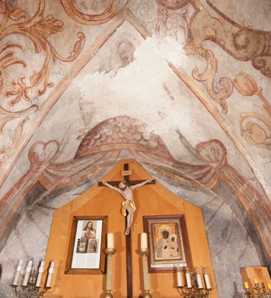 Zdjęcie nr 3: Polichromia pokrywa ściany i sklepienie kolebkowe z lunetami czworobocznej, dwuprzęsłowej zakrystii. Pole sklepienia wypełnia dekoracja ornamentalna utworzona ze zawijanych liści akantu, stylizowanych kwiatów oraz wazonów z kwiatami. Pośrodku sklepienia umieszczono w owalu w kartuszu fragmentarycznie zachowaną scenę Koronacji Marii. W centrum kompozycji zachowała się głowa Marii ujęta w trzy czwarte w prawo z widocznym fragmentem prawego ramienia i ułożonej do modlitwy prawej ręki. Po prawej stronie widać postać tronującego Boga Ojca w złotej koronie, z brodą, trzymającego złotą koronę nad głową Marii. Z lewej można dostrzec fragment ręki Chrystusa oraz fragment jego czerwonej szaty i lewej stopy. Na ścianie wschodniej dekorację malarską w postaci wici utworzonej ze stylizowanych liści akantu i kwiatów poprowadzono w glifie okiennym. Wokół okna utworzono malowane obramienie z motywami stylizowanego ornamentu rollwerkowego. Ponad oknem w glifie znajduje się malowany chrystogram "IHS". Po prawej stronie okna widoczne jest całopostaciowe przedstawienie proroka Eliasza z rozłożonymi rękami. Postać została ujęta w trzech czwartych w prawo. Ma pociągłą twarz okoloną zarostem z wydatnym nosem i ustami. Ubrana jest w strój wschodni - długą szatę z bladoczerwonym płaszczem z kołnierzykiem spiętym przy szyi oraz z rozciętymi rękawami. Na głowie ma szaroniebieski turban. Ponad nim widać lecącego kruka. Obok mężczyzny z prawej strony widoczna jest niewielka sekwencja krajobrazowa z motywem drzewa. Eliasz zwrócony jest w stronę sceny z Ostatnią Wieczerzą wykonaną w pierwszym przęśle ściany południowej zakrystii. Ostatnią Wieczerzę z prawej strony zamyka malowana kolumna z kapitelem rozdzielająca ścianę na dwa przęsła. Na tle altany ze schodami po lewej, flankowanej trzema kolumnami na wysokich cokołach, ukazano Chrystusa i dwunastu apostołów siedzący przy okrągłym, okazałym stole. Ponad stołem wisi płonącą lampa. Stół nakryto białym obrusem zastawionym siedmioma talerzami, owalną misą pośrodku, trzema okrągłymi bochenkami chleba, dwoma nożami i kielichem. Siedzący centralnie za stołem Chrystus został ukazany frontalnie. Zbawiciel ma zmęczoną twarz otoczoną brodą i długimi włosami, spływającymi na ramiona. Ubrany jest w białą tunikę i niebieski płaszcz przerzucony przez lewe ramię. O jego pierś opiera się zamyślony św. Jan, wspierający głowę na prawej ręce trzymanej na stole. Lewą rękę położoną na blacie ma zgiętą w łokciu. Wokół stołu siedzą rozmawiający ze sobą pozostali apostołowie. Są to starsi, brodaci mężczyźni, niektórzy z nich są łysi. Ubrani są w tuniki i narzucone na ramionach płaszcze. Można spośród nich wyróżnić siedzącego po prawe strony Chrystusa św. Piotra oraz Judasza widocznego jako pierwszego po lewej stronie kompozycji. Judasza ukazanego frontalnie identyfikuje żółta szata oraz trzymany w prawej ręce mieszek ze srebnikami. Powyżej w podłuczu lunety namalowano siedzącego, starszego brodatego mężczyznę ujętego w trzech czwartych w prawo. Jest to ewangelista widoczny do kolan. Prawą rękę przyciska do piersi lewą zaś opiera o stół ustawiony z prawej strony kompozycji z ułożoną na nim księgą. Jego twarz charakteryzuje wydatny nos i usta oraz spojrzenie skierowane na widza. W drugim przęśle ściany  
południowej dekoracje tworzy stylizowana wić akantowo-kwiatowa w glifie okiennym oraz otaczające okno obramienie utworzone z motywów rollwerkowych. Nie zachowała się polichromia w lunecie powyżej okna. Na zachodniej ścianie w glifie dawnego otworu wejściowego obramionego żółtą listwą, wykonano dekorację malarską składającą się z malowanych romboidalnych płycin pokrytych czerwonawą marmoryzacją. Ponad glifem na ścianie znajduje się czerwony krzyż równoramienny rozdzielający datę 16 / 46. Na ścianie z prawej strony otworu wyobrażono Ukrzyżowanie Chrystusa na polu pokrytym licznymi, stojącymi krzyżami. Postać Zbawiciela zachowała się fragmentarycznie w partii tułowia i nóg. Powyżej pole w lunecie ozdobiono stylizowaną wicią akantowo-kwiatową. Ścianę północną w pierwszym przęśle wypełnionym szafą zakrystyjną udekorowano rozpostartym, czerwonym paludamentum z baldachimem. Powyżej w lunecie zachowało się bardzo zniszczone przedstawienie św. Jana Ewangelisty, którego można rozpoznać po młodzieńczej, pociągłej twarz o wydatnych rysach. Z postaci zachowały się jeszcze  fragmenty stóp widoczne nad baldachimem. W drugim prześle w dolnej strefie przepruto drzwi z otworem zamkniętym łukiem odcinkowym, obramienionym złocistą taśmą. W nadprożu znalazła się stylizowana wić akantowo-kwiatowa. Powyżej, w górnej strefie namalowano modlitwę Chrystusa w Ogrójcu. Na pierwszym planie kompozycji widoczny jest klęczący na ziemi Zbawiciel ujęty w trzech czwartych w prawo. Lewą rękę ma przyłożoną do piersi, drugą zaś odsuniętą od tułowia. Jego uniesioną głowę ku górze otacza ciemna broda i długie włosy spływające na plecy. Chrystus ma wydatny nos i usta. Ubrany jest w obszerną, jasnooliwkową tunikę przewiązaną w pasie oraz niebieskoszary płaszcz przerzucony przez lewe ramię i rękę. Jezus wpatruje się w zjawiającego mu się powyżej uskrzydlonego anioła ukazanego w dwóch trzecich na obłokach. Anioł w wyciągniętej prawej ręce trzyma złoty kielich, a prawą podtrzymuje opary o ramię krzyż. Ubrany jest w baldoczerwoną tunikę przewiązaną w pasie. Z prawej strony Jezusa widocznych jest trzech śpiących apostołów. Na pierwszym planie ukazano leżącego św. Piotra z głową wspartą na lewej ręce. Jest to starszy mężczyzna z łysym czołem i siwiejącymi włosami i brodą. Ubrany jest w bladoniebieską tunikę i ciemnoochrowy płaszcz. Za nim widać siedzącego św. Jana z głową wspartą na ręce, którą podpiera o prawe kolano. Jest to młodzieniec o długich włosach, ubrany w blado oliwkową tunikę i baldoczerwony płaszcz. O niewielki wzgórek z lewej strony Jana oparty jest św. Jakub. Jest to starszy mężczyzna z brązową brodą i włosami ubrany w bladooliwkowy płaszcz. Za Zbawicielem z lewej strony kompozycji widać drewniany płot z bramką, przez którą do ogrodu wchodzi Judasz w jasno-chórowej szacie, prowadzący zbrojny oddział sług świątynnych. W głębi kompozycji ukazano panoramę Jerozolimy. Powyżej na sklepieniu lunety wyobrażono siedzącego ewangelistę, który ukazany został jako starzec z długą siwą brodą i łysiejącym czołem. Mężczyzna wspierając prawą rękę o stół podpiera nią głowę. Lewą ma położoną na kolanie. Ubrany jest w szarą tunikę oraz bladoczerwony płaszcz przerzucony przez prawe ramię i okrywający kolana.    
