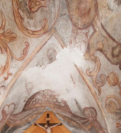 Zdjęcie nr 20: Polichromia pokrywa ściany i sklepienie kolebkowe z lunetami czworobocznej, dwuprzęsłowej zakrystii. Pole sklepienia wypełnia dekoracja ornamentalna utworzona ze zawijanych liści akantu, stylizowanych kwiatów oraz wazonów z kwiatami. Pośrodku sklepienia umieszczono w owalu w kartuszu fragmentarycznie zachowaną scenę Koronacji Marii. W centrum kompozycji zachowała się głowa Marii ujęta w trzy czwarte w prawo z widocznym fragmentem prawego ramienia i ułożonej do modlitwy prawej ręki. Po prawej stronie widać postać tronującego Boga Ojca w złotej koronie, z brodą, trzymającego złotą koronę nad głową Marii. Z lewej można dostrzec fragment ręki Chrystusa oraz fragment jego czerwonej szaty i lewej stopy. Na ścianie wschodniej dekorację malarską w postaci wici utworzonej ze stylizowanych liści akantu i kwiatów poprowadzono w glifie okiennym. Wokół okna utworzono malowane obramienie z motywami stylizowanego ornamentu rollwerkowego. Ponad oknem w glifie znajduje się malowany chrystogram "IHS". Po prawej stronie okna widoczne jest całopostaciowe przedstawienie proroka Eliasza z rozłożonymi rękami. Postać została ujęta w trzech czwartych w prawo. Ma pociągłą twarz okoloną zarostem z wydatnym nosem i ustami. Ubrana jest w strój wschodni - długą szatę z bladoczerwonym płaszczem z kołnierzykiem spiętym przy szyi oraz z rozciętymi rękawami. Na głowie ma szaroniebieski turban. Ponad nim widać lecącego kruka. Obok mężczyzny z prawej strony widoczna jest niewielka sekwencja krajobrazowa z motywem drzewa. Eliasz zwrócony jest w stronę sceny z Ostatnią Wieczerzą wykonaną w pierwszym przęśle ściany południowej zakrystii. Ostatnią Wieczerzę z prawej strony zamyka malowana kolumna z kapitelem rozdzielająca ścianę na dwa przęsła. Na tle altany ze schodami po lewej, flankowanej trzema kolumnami na wysokich cokołach, ukazano Chrystusa i dwunastu apostołów siedzący przy okrągłym, okazałym stole. Ponad stołem wisi płonącą lampa. Stół nakryto białym obrusem zastawionym siedmioma talerzami, owalną misą pośrodku, trzema okrągłymi bochenkami chleba, dwoma nożami i kielichem. Siedzący centralnie za stołem Chrystus został ukazany frontalnie. Zbawiciel ma zmęczoną twarz otoczoną brodą i długimi włosami, spływającymi na ramiona. Ubrany jest w białą tunikę i niebieski płaszcz przerzucony przez lewe ramię. O jego pierś opiera się zamyślony św. Jan, wspierający głowę na prawej ręce trzymanej na stole. Lewą rękę położoną na blacie ma zgiętą w łokciu. Wokół stołu siedzą rozmawiający ze sobą pozostali apostołowie. Są to starsi, brodaci mężczyźni, niektórzy z nich są łysi. Ubrani są w tuniki i narzucone na ramionach płaszcze. Można spośród nich wyróżnić siedzącego po prawe strony Chrystusa św. Piotra oraz Judasza widocznego jako pierwszego po lewej stronie kompozycji. Judasza ukazanego frontalnie identyfikuje żółta szata oraz trzymany w prawej ręce mieszek ze srebnikami. Powyżej w podłuczu lunety namalowano siedzącego, starszego brodatego mężczyznę ujętego w trzech czwartych w prawo. Jest to ewangelista widoczny do kolan. Prawą rękę przyciska do piersi lewą zaś opiera o stół ustawiony z prawej strony kompozycji z ułożoną na nim księgą. Jego twarz charakteryzuje wydatny nos i usta oraz spojrzenie skierowane na widza. W drugim przęśle ściany  
południowej dekoracje tworzy stylizowana wić akantowo-kwiatowa w glifie okiennym oraz otaczające okno obramienie utworzone z motywów rollwerkowych. Nie zachowała się polichromia w lunecie powyżej okna. Na zachodniej ścianie w glifie dawnego otworu wejściowego obramionego żółtą listwą, wykonano dekorację malarską składającą się z malowanych romboidalnych płycin pokrytych czerwonawą marmoryzacją. Ponad glifem na ścianie znajduje się czerwony krzyż równoramienny rozdzielający datę 16 / 46. Na ścianie z prawej strony otworu wyobrażono Ukrzyżowanie Chrystusa na polu pokrytym licznymi, stojącymi krzyżami. Postać Zbawiciela zachowała się fragmentarycznie w partii tułowia i nóg. Powyżej pole w lunecie ozdobiono stylizowaną wicią akantowo-kwiatową. Ścianę północną w pierwszym przęśle wypełnionym szafą zakrystyjną udekorowano rozpostartym, czerwonym paludamentum z baldachimem. Powyżej w lunecie zachowało się bardzo zniszczone przedstawienie św. Jana Ewangelisty, którego można rozpoznać po młodzieńczej, pociągłej twarz o wydatnych rysach. Z postaci zachowały się jeszcze  fragmenty stóp widoczne nad baldachimem. W drugim prześle w dolnej strefie przepruto drzwi z otworem zamkniętym łukiem odcinkowym, obramienionym złocistą taśmą. W nadprożu znalazła się stylizowana wić akantowo-kwiatowa. Powyżej, w górnej strefie namalowano modlitwę Chrystusa w Ogrójcu. Na pierwszym planie kompozycji widoczny jest klęczący na ziemi Zbawiciel ujęty w trzech czwartych w prawo. Lewą rękę ma przyłożoną do piersi, drugą zaś odsuniętą od tułowia. Jego uniesioną głowę ku górze otacza ciemna broda i długie włosy spływające na plecy. Chrystus ma wydatny nos i usta. Ubrany jest w obszerną, jasnooliwkową tunikę przewiązaną w pasie oraz niebieskoszary płaszcz przerzucony przez lewe ramię i rękę. Jezus wpatruje się w zjawiającego mu się powyżej uskrzydlonego anioła ukazanego w dwóch trzecich na obłokach. Anioł w wyciągniętej prawej ręce trzyma złoty kielich, a prawą podtrzymuje opary o ramię krzyż. Ubrany jest w baldoczerwoną tunikę przewiązaną w pasie. Z prawej strony Jezusa widocznych jest trzech śpiących apostołów. Na pierwszym planie ukazano leżącego św. Piotra z głową wspartą na lewej ręce. Jest to starszy mężczyzna z łysym czołem i siwiejącymi włosami i brodą. Ubrany jest w bladoniebieską tunikę i ciemnoochrowy płaszcz. Za nim widać siedzącego św. Jana z głową wspartą na ręce, którą podpiera o prawe kolano. Jest to młodzieniec o długich włosach, ubrany w blado oliwkową tunikę i baldoczerwony płaszcz. O niewielki wzgórek z lewej strony Jana oparty jest św. Jakub. Jest to starszy mężczyzna z brązową brodą i włosami ubrany w bladooliwkowy płaszcz. Za Zbawicielem z lewej strony kompozycji widać drewniany płot z bramką, przez którą do ogrodu wchodzi Judasz w jasno-chórowej szacie, prowadzący zbrojny oddział sług świątynnych. W głębi kompozycji ukazano panoramę Jerozolimy. Powyżej na sklepieniu lunety wyobrażono siedzącego ewangelistę, który ukazany został jako starzec z długą siwą brodą i łysiejącym czołem. Mężczyzna wspierając prawą rękę o stół podpiera nią głowę. Lewą ma położoną na kolanie. Ubrany jest w szarą tunikę oraz bladoczerwony płaszcz przerzucony przez prawe ramię i okrywający kolana.    
