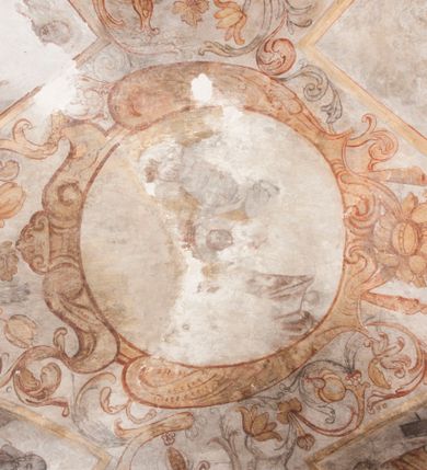 Zdjęcie nr 25: Polichromia pokrywa ściany i sklepienie kolebkowe z lunetami czworobocznej, dwuprzęsłowej zakrystii. Pole sklepienia wypełnia dekoracja ornamentalna utworzona ze zawijanych liści akantu, stylizowanych kwiatów oraz wazonów z kwiatami. Pośrodku sklepienia umieszczono w owalu w kartuszu fragmentarycznie zachowaną scenę Koronacji Marii. W centrum kompozycji zachowała się głowa Marii ujęta w trzy czwarte w prawo z widocznym fragmentem prawego ramienia i ułożonej do modlitwy prawej ręki. Po prawej stronie widać postać tronującego Boga Ojca w złotej koronie, z brodą, trzymającego złotą koronę nad głową Marii. Z lewej można dostrzec fragment ręki Chrystusa oraz fragment jego czerwonej szaty i lewej stopy. Na ścianie wschodniej dekorację malarską w postaci wici utworzonej ze stylizowanych liści akantu i kwiatów poprowadzono w glifie okiennym. Wokół okna utworzono malowane obramienie z motywami stylizowanego ornamentu rollwerkowego. Ponad oknem w glifie znajduje się malowany chrystogram "IHS". Po prawej stronie okna widoczne jest całopostaciowe przedstawienie proroka Eliasza z rozłożonymi rękami. Postać została ujęta w trzech czwartych w prawo. Ma pociągłą twarz okoloną zarostem z wydatnym nosem i ustami. Ubrana jest w strój wschodni - długą szatę z bladoczerwonym płaszczem z kołnierzykiem spiętym przy szyi oraz z rozciętymi rękawami. Na głowie ma szaroniebieski turban. Ponad nim widać lecącego kruka. Obok mężczyzny z prawej strony widoczna jest niewielka sekwencja krajobrazowa z motywem drzewa. Eliasz zwrócony jest w stronę sceny z Ostatnią Wieczerzą wykonaną w pierwszym przęśle ściany południowej zakrystii. Ostatnią Wieczerzę z prawej strony zamyka malowana kolumna z kapitelem rozdzielająca ścianę na dwa przęsła. Na tle altany ze schodami po lewej, flankowanej trzema kolumnami na wysokich cokołach, ukazano Chrystusa i dwunastu apostołów siedzący przy okrągłym, okazałym stole. Ponad stołem wisi płonącą lampa. Stół nakryto białym obrusem zastawionym siedmioma talerzami, owalną misą pośrodku, trzema okrągłymi bochenkami chleba, dwoma nożami i kielichem. Siedzący centralnie za stołem Chrystus został ukazany frontalnie. Zbawiciel ma zmęczoną twarz otoczoną brodą i długimi włosami, spływającymi na ramiona. Ubrany jest w białą tunikę i niebieski płaszcz przerzucony przez lewe ramię. O jego pierś opiera się zamyślony św. Jan, wspierający głowę na prawej ręce trzymanej na stole. Lewą rękę położoną na blacie ma zgiętą w łokciu. Wokół stołu siedzą rozmawiający ze sobą pozostali apostołowie. Są to starsi, brodaci mężczyźni, niektórzy z nich są łysi. Ubrani są w tuniki i narzucone na ramionach płaszcze. Można spośród nich wyróżnić siedzącego po prawe strony Chrystusa św. Piotra oraz Judasza widocznego jako pierwszego po lewej stronie kompozycji. Judasza ukazanego frontalnie identyfikuje żółta szata oraz trzymany w prawej ręce mieszek ze srebnikami. Powyżej w podłuczu lunety namalowano siedzącego, starszego brodatego mężczyznę ujętego w trzech czwartych w prawo. Jest to ewangelista widoczny do kolan. Prawą rękę przyciska do piersi lewą zaś opiera o stół ustawiony z prawej strony kompozycji z ułożoną na nim księgą. Jego twarz charakteryzuje wydatny nos i usta oraz spojrzenie skierowane na widza. W drugim przęśle ściany  
południowej dekoracje tworzy stylizowana wić akantowo-kwiatowa w glifie okiennym oraz otaczające okno obramienie utworzone z motywów rollwerkowych. Nie zachowała się polichromia w lunecie powyżej okna. Na zachodniej ścianie w glifie dawnego otworu wejściowego obramionego żółtą listwą, wykonano dekorację malarską składającą się z malowanych romboidalnych płycin pokrytych czerwonawą marmoryzacją. Ponad glifem na ścianie znajduje się czerwony krzyż równoramienny rozdzielający datę 16 / 46. Na ścianie z prawej strony otworu wyobrażono Ukrzyżowanie Chrystusa na polu pokrytym licznymi, stojącymi krzyżami. Postać Zbawiciela zachowała się fragmentarycznie w partii tułowia i nóg. Powyżej pole w lunecie ozdobiono stylizowaną wicią akantowo-kwiatową. Ścianę północną w pierwszym przęśle wypełnionym szafą zakrystyjną udekorowano rozpostartym, czerwonym paludamentum z baldachimem. Powyżej w lunecie zachowało się bardzo zniszczone przedstawienie św. Jana Ewangelisty, którego można rozpoznać po młodzieńczej, pociągłej twarz o wydatnych rysach. Z postaci zachowały się jeszcze  fragmenty stóp widoczne nad baldachimem. W drugim prześle w dolnej strefie przepruto drzwi z otworem zamkniętym łukiem odcinkowym, obramienionym złocistą taśmą. W nadprożu znalazła się stylizowana wić akantowo-kwiatowa. Powyżej, w górnej strefie namalowano modlitwę Chrystusa w Ogrójcu. Na pierwszym planie kompozycji widoczny jest klęczący na ziemi Zbawiciel ujęty w trzech czwartych w prawo. Lewą rękę ma przyłożoną do piersi, drugą zaś odsuniętą od tułowia. Jego uniesioną głowę ku górze otacza ciemna broda i długie włosy spływające na plecy. Chrystus ma wydatny nos i usta. Ubrany jest w obszerną, jasnooliwkową tunikę przewiązaną w pasie oraz niebieskoszary płaszcz przerzucony przez lewe ramię i rękę. Jezus wpatruje się w zjawiającego mu się powyżej uskrzydlonego anioła ukazanego w dwóch trzecich na obłokach. Anioł w wyciągniętej prawej ręce trzyma złoty kielich, a prawą podtrzymuje opary o ramię krzyż. Ubrany jest w baldoczerwoną tunikę przewiązaną w pasie. Z prawej strony Jezusa widocznych jest trzech śpiących apostołów. Na pierwszym planie ukazano leżącego św. Piotra z głową wspartą na lewej ręce. Jest to starszy mężczyzna z łysym czołem i siwiejącymi włosami i brodą. Ubrany jest w bladoniebieską tunikę i ciemnoochrowy płaszcz. Za nim widać siedzącego św. Jana z głową wspartą na ręce, którą podpiera o prawe kolano. Jest to młodzieniec o długich włosach, ubrany w blado oliwkową tunikę i baldoczerwony płaszcz. O niewielki wzgórek z lewej strony Jana oparty jest św. Jakub. Jest to starszy mężczyzna z brązową brodą i włosami ubrany w bladooliwkowy płaszcz. Za Zbawicielem z lewej strony kompozycji widać drewniany płot z bramką, przez którą do ogrodu wchodzi Judasz w jasno-chórowej szacie, prowadzący zbrojny oddział sług świątynnych. W głębi kompozycji ukazano panoramę Jerozolimy. Powyżej na sklepieniu lunety wyobrażono siedzącego ewangelistę, który ukazany został jako starzec z długą siwą brodą i łysiejącym czołem. Mężczyzna wspierając prawą rękę o stół podpiera nią głowę. Lewą ma położoną na kolanie. Ubrany jest w szarą tunikę oraz bladoczerwony płaszcz przerzucony przez prawe ramię i okrywający kolana.    
