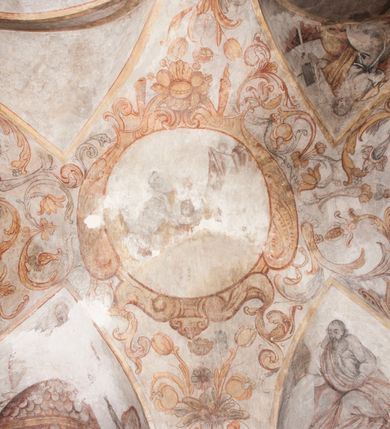 Zdjęcie nr 26: Polichromia pokrywa ściany i sklepienie kolebkowe z lunetami czworobocznej, dwuprzęsłowej zakrystii. Pole sklepienia wypełnia dekoracja ornamentalna utworzona ze zawijanych liści akantu, stylizowanych kwiatów oraz wazonów z kwiatami. Pośrodku sklepienia umieszczono w owalu w kartuszu fragmentarycznie zachowaną scenę Koronacji Marii. W centrum kompozycji zachowała się głowa Marii ujęta w trzy czwarte w prawo z widocznym fragmentem prawego ramienia i ułożonej do modlitwy prawej ręki. Po prawej stronie widać postać tronującego Boga Ojca w złotej koronie, z brodą, trzymającego złotą koronę nad głową Marii. Z lewej można dostrzec fragment ręki Chrystusa oraz fragment jego czerwonej szaty i lewej stopy. Na ścianie wschodniej dekorację malarską w postaci wici utworzonej ze stylizowanych liści akantu i kwiatów poprowadzono w glifie okiennym. Wokół okna utworzono malowane obramienie z motywami stylizowanego ornamentu rollwerkowego. Ponad oknem w glifie znajduje się malowany chrystogram "IHS". Po prawej stronie okna widoczne jest całopostaciowe przedstawienie proroka Eliasza z rozłożonymi rękami. Postać została ujęta w trzech czwartych w prawo. Ma pociągłą twarz okoloną zarostem z wydatnym nosem i ustami. Ubrana jest w strój wschodni - długą szatę z bladoczerwonym płaszczem z kołnierzykiem spiętym przy szyi oraz z rozciętymi rękawami. Na głowie ma szaroniebieski turban. Ponad nim widać lecącego kruka. Obok mężczyzny z prawej strony widoczna jest niewielka sekwencja krajobrazowa z motywem drzewa. Eliasz zwrócony jest w stronę sceny z Ostatnią Wieczerzą wykonaną w pierwszym przęśle ściany południowej zakrystii. Ostatnią Wieczerzę z prawej strony zamyka malowana kolumna z kapitelem rozdzielająca ścianę na dwa przęsła. Na tle altany ze schodami po lewej, flankowanej trzema kolumnami na wysokich cokołach, ukazano Chrystusa i dwunastu apostołów siedzący przy okrągłym, okazałym stole. Ponad stołem wisi płonącą lampa. Stół nakryto białym obrusem zastawionym siedmioma talerzami, owalną misą pośrodku, trzema okrągłymi bochenkami chleba, dwoma nożami i kielichem. Siedzący centralnie za stołem Chrystus został ukazany frontalnie. Zbawiciel ma zmęczoną twarz otoczoną brodą i długimi włosami, spływającymi na ramiona. Ubrany jest w białą tunikę i niebieski płaszcz przerzucony przez lewe ramię. O jego pierś opiera się zamyślony św. Jan, wspierający głowę na prawej ręce trzymanej na stole. Lewą rękę położoną na blacie ma zgiętą w łokciu. Wokół stołu siedzą rozmawiający ze sobą pozostali apostołowie. Są to starsi, brodaci mężczyźni, niektórzy z nich są łysi. Ubrani są w tuniki i narzucone na ramionach płaszcze. Można spośród nich wyróżnić siedzącego po prawe strony Chrystusa św. Piotra oraz Judasza widocznego jako pierwszego po lewej stronie kompozycji. Judasza ukazanego frontalnie identyfikuje żółta szata oraz trzymany w prawej ręce mieszek ze srebnikami. Powyżej w podłuczu lunety namalowano siedzącego, starszego brodatego mężczyznę ujętego w trzech czwartych w prawo. Jest to ewangelista widoczny do kolan. Prawą rękę przyciska do piersi lewą zaś opiera o stół ustawiony z prawej strony kompozycji z ułożoną na nim księgą. Jego twarz charakteryzuje wydatny nos i usta oraz spojrzenie skierowane na widza. W drugim przęśle ściany  
południowej dekoracje tworzy stylizowana wić akantowo-kwiatowa w glifie okiennym oraz otaczające okno obramienie utworzone z motywów rollwerkowych. Nie zachowała się polichromia w lunecie powyżej okna. Na zachodniej ścianie w glifie dawnego otworu wejściowego obramionego żółtą listwą, wykonano dekorację malarską składającą się z malowanych romboidalnych płycin pokrytych czerwonawą marmoryzacją. Ponad glifem na ścianie znajduje się czerwony krzyż równoramienny rozdzielający datę 16 / 46. Na ścianie z prawej strony otworu wyobrażono Ukrzyżowanie Chrystusa na polu pokrytym licznymi, stojącymi krzyżami. Postać Zbawiciela zachowała się fragmentarycznie w partii tułowia i nóg. Powyżej pole w lunecie ozdobiono stylizowaną wicią akantowo-kwiatową. Ścianę północną w pierwszym przęśle wypełnionym szafą zakrystyjną udekorowano rozpostartym, czerwonym paludamentum z baldachimem. Powyżej w lunecie zachowało się bardzo zniszczone przedstawienie św. Jana Ewangelisty, którego można rozpoznać po młodzieńczej, pociągłej twarz o wydatnych rysach. Z postaci zachowały się jeszcze  fragmenty stóp widoczne nad baldachimem. W drugim prześle w dolnej strefie przepruto drzwi z otworem zamkniętym łukiem odcinkowym, obramienionym złocistą taśmą. W nadprożu znalazła się stylizowana wić akantowo-kwiatowa. Powyżej, w górnej strefie namalowano modlitwę Chrystusa w Ogrójcu. Na pierwszym planie kompozycji widoczny jest klęczący na ziemi Zbawiciel ujęty w trzech czwartych w prawo. Lewą rękę ma przyłożoną do piersi, drugą zaś odsuniętą od tułowia. Jego uniesioną głowę ku górze otacza ciemna broda i długie włosy spływające na plecy. Chrystus ma wydatny nos i usta. Ubrany jest w obszerną, jasnooliwkową tunikę przewiązaną w pasie oraz niebieskoszary płaszcz przerzucony przez lewe ramię i rękę. Jezus wpatruje się w zjawiającego mu się powyżej uskrzydlonego anioła ukazanego w dwóch trzecich na obłokach. Anioł w wyciągniętej prawej ręce trzyma złoty kielich, a prawą podtrzymuje opary o ramię krzyż. Ubrany jest w baldoczerwoną tunikę przewiązaną w pasie. Z prawej strony Jezusa widocznych jest trzech śpiących apostołów. Na pierwszym planie ukazano leżącego św. Piotra z głową wspartą na lewej ręce. Jest to starszy mężczyzna z łysym czołem i siwiejącymi włosami i brodą. Ubrany jest w bladoniebieską tunikę i ciemnoochrowy płaszcz. Za nim widać siedzącego św. Jana z głową wspartą na ręce, którą podpiera o prawe kolano. Jest to młodzieniec o długich włosach, ubrany w blado oliwkową tunikę i baldoczerwony płaszcz. O niewielki wzgórek z lewej strony Jana oparty jest św. Jakub. Jest to starszy mężczyzna z brązową brodą i włosami ubrany w bladooliwkowy płaszcz. Za Zbawicielem z lewej strony kompozycji widać drewniany płot z bramką, przez którą do ogrodu wchodzi Judasz w jasno-chórowej szacie, prowadzący zbrojny oddział sług świątynnych. W głębi kompozycji ukazano panoramę Jerozolimy. Powyżej na sklepieniu lunety wyobrażono siedzącego ewangelistę, który ukazany został jako starzec z długą siwą brodą i łysiejącym czołem. Mężczyzna wspierając prawą rękę o stół podpiera nią głowę. Lewą ma położoną na kolanie. Ubrany jest w szarą tunikę oraz bladoczerwony płaszcz przerzucony przez prawe ramię i okrywający kolana.    
