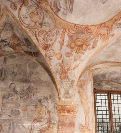 Zdjęcie nr 28: Polichromia pokrywa ściany i sklepienie kolebkowe z lunetami czworobocznej, dwuprzęsłowej zakrystii. Pole sklepienia wypełnia dekoracja ornamentalna utworzona ze zawijanych liści akantu, stylizowanych kwiatów oraz wazonów z kwiatami. Pośrodku sklepienia umieszczono w owalu w kartuszu fragmentarycznie zachowaną scenę Koronacji Marii. W centrum kompozycji zachowała się głowa Marii ujęta w trzy czwarte w prawo z widocznym fragmentem prawego ramienia i ułożonej do modlitwy prawej ręki. Po prawej stronie widać postać tronującego Boga Ojca w złotej koronie, z brodą, trzymającego złotą koronę nad głową Marii. Z lewej można dostrzec fragment ręki Chrystusa oraz fragment jego czerwonej szaty i lewej stopy. Na ścianie wschodniej dekorację malarską w postaci wici utworzonej ze stylizowanych liści akantu i kwiatów poprowadzono w glifie okiennym. Wokół okna utworzono malowane obramienie z motywami stylizowanego ornamentu rollwerkowego. Ponad oknem w glifie znajduje się malowany chrystogram "IHS". Po prawej stronie okna widoczne jest całopostaciowe przedstawienie proroka Eliasza z rozłożonymi rękami. Postać została ujęta w trzech czwartych w prawo. Ma pociągłą twarz okoloną zarostem z wydatnym nosem i ustami. Ubrana jest w strój wschodni - długą szatę z bladoczerwonym płaszczem z kołnierzykiem spiętym przy szyi oraz z rozciętymi rękawami. Na głowie ma szaroniebieski turban. Ponad nim widać lecącego kruka. Obok mężczyzny z prawej strony widoczna jest niewielka sekwencja krajobrazowa z motywem drzewa. Eliasz zwrócony jest w stronę sceny z Ostatnią Wieczerzą wykonaną w pierwszym przęśle ściany południowej zakrystii. Ostatnią Wieczerzę z prawej strony zamyka malowana kolumna z kapitelem rozdzielająca ścianę na dwa przęsła. Na tle altany ze schodami po lewej, flankowanej trzema kolumnami na wysokich cokołach, ukazano Chrystusa i dwunastu apostołów siedzący przy okrągłym, okazałym stole. Ponad stołem wisi płonącą lampa. Stół nakryto białym obrusem zastawionym siedmioma talerzami, owalną misą pośrodku, trzema okrągłymi bochenkami chleba, dwoma nożami i kielichem. Siedzący centralnie za stołem Chrystus został ukazany frontalnie. Zbawiciel ma zmęczoną twarz otoczoną brodą i długimi włosami, spływającymi na ramiona. Ubrany jest w białą tunikę i niebieski płaszcz przerzucony przez lewe ramię. O jego pierś opiera się zamyślony św. Jan, wspierający głowę na prawej ręce trzymanej na stole. Lewą rękę położoną na blacie ma zgiętą w łokciu. Wokół stołu siedzą rozmawiający ze sobą pozostali apostołowie. Są to starsi, brodaci mężczyźni, niektórzy z nich są łysi. Ubrani są w tuniki i narzucone na ramionach płaszcze. Można spośród nich wyróżnić siedzącego po prawe strony Chrystusa św. Piotra oraz Judasza widocznego jako pierwszego po lewej stronie kompozycji. Judasza ukazanego frontalnie identyfikuje żółta szata oraz trzymany w prawej ręce mieszek ze srebnikami. Powyżej w podłuczu lunety namalowano siedzącego, starszego brodatego mężczyznę ujętego w trzech czwartych w prawo. Jest to ewangelista widoczny do kolan. Prawą rękę przyciska do piersi lewą zaś opiera o stół ustawiony z prawej strony kompozycji z ułożoną na nim księgą. Jego twarz charakteryzuje wydatny nos i usta oraz spojrzenie skierowane na widza. W drugim przęśle ściany  
południowej dekoracje tworzy stylizowana wić akantowo-kwiatowa w glifie okiennym oraz otaczające okno obramienie utworzone z motywów rollwerkowych. Nie zachowała się polichromia w lunecie powyżej okna. Na zachodniej ścianie w glifie dawnego otworu wejściowego obramionego żółtą listwą, wykonano dekorację malarską składającą się z malowanych romboidalnych płycin pokrytych czerwonawą marmoryzacją. Ponad glifem na ścianie znajduje się czerwony krzyż równoramienny rozdzielający datę 16 / 46. Na ścianie z prawej strony otworu wyobrażono Ukrzyżowanie Chrystusa na polu pokrytym licznymi, stojącymi krzyżami. Postać Zbawiciela zachowała się fragmentarycznie w partii tułowia i nóg. Powyżej pole w lunecie ozdobiono stylizowaną wicią akantowo-kwiatową. Ścianę północną w pierwszym przęśle wypełnionym szafą zakrystyjną udekorowano rozpostartym, czerwonym paludamentum z baldachimem. Powyżej w lunecie zachowało się bardzo zniszczone przedstawienie św. Jana Ewangelisty, którego można rozpoznać po młodzieńczej, pociągłej twarz o wydatnych rysach. Z postaci zachowały się jeszcze  fragmenty stóp widoczne nad baldachimem. W drugim prześle w dolnej strefie przepruto drzwi z otworem zamkniętym łukiem odcinkowym, obramienionym złocistą taśmą. W nadprożu znalazła się stylizowana wić akantowo-kwiatowa. Powyżej, w górnej strefie namalowano modlitwę Chrystusa w Ogrójcu. Na pierwszym planie kompozycji widoczny jest klęczący na ziemi Zbawiciel ujęty w trzech czwartych w prawo. Lewą rękę ma przyłożoną do piersi, drugą zaś odsuniętą od tułowia. Jego uniesioną głowę ku górze otacza ciemna broda i długie włosy spływające na plecy. Chrystus ma wydatny nos i usta. Ubrany jest w obszerną, jasnooliwkową tunikę przewiązaną w pasie oraz niebieskoszary płaszcz przerzucony przez lewe ramię i rękę. Jezus wpatruje się w zjawiającego mu się powyżej uskrzydlonego anioła ukazanego w dwóch trzecich na obłokach. Anioł w wyciągniętej prawej ręce trzyma złoty kielich, a prawą podtrzymuje opary o ramię krzyż. Ubrany jest w baldoczerwoną tunikę przewiązaną w pasie. Z prawej strony Jezusa widocznych jest trzech śpiących apostołów. Na pierwszym planie ukazano leżącego św. Piotra z głową wspartą na lewej ręce. Jest to starszy mężczyzna z łysym czołem i siwiejącymi włosami i brodą. Ubrany jest w bladoniebieską tunikę i ciemnoochrowy płaszcz. Za nim widać siedzącego św. Jana z głową wspartą na ręce, którą podpiera o prawe kolano. Jest to młodzieniec o długich włosach, ubrany w blado oliwkową tunikę i baldoczerwony płaszcz. O niewielki wzgórek z lewej strony Jana oparty jest św. Jakub. Jest to starszy mężczyzna z brązową brodą i włosami ubrany w bladooliwkowy płaszcz. Za Zbawicielem z lewej strony kompozycji widać drewniany płot z bramką, przez którą do ogrodu wchodzi Judasz w jasno-chórowej szacie, prowadzący zbrojny oddział sług świątynnych. W głębi kompozycji ukazano panoramę Jerozolimy. Powyżej na sklepieniu lunety wyobrażono siedzącego ewangelistę, który ukazany został jako starzec z długą siwą brodą i łysiejącym czołem. Mężczyzna wspierając prawą rękę o stół podpiera nią głowę. Lewą ma położoną na kolanie. Ubrany jest w szarą tunikę oraz bladoczerwony płaszcz przerzucony przez prawe ramię i okrywający kolana.    
