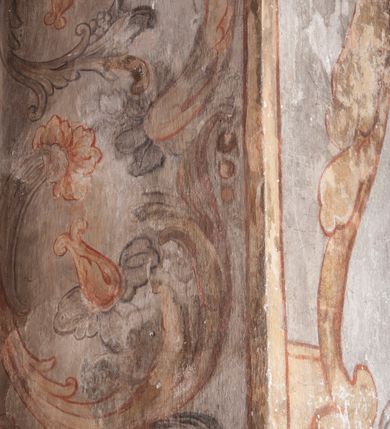 Zdjęcie nr 29: Polichromia pokrywa ściany i sklepienie kolebkowe z lunetami czworobocznej, dwuprzęsłowej zakrystii. Pole sklepienia wypełnia dekoracja ornamentalna utworzona ze zawijanych liści akantu, stylizowanych kwiatów oraz wazonów z kwiatami. Pośrodku sklepienia umieszczono w owalu w kartuszu fragmentarycznie zachowaną scenę Koronacji Marii. W centrum kompozycji zachowała się głowa Marii ujęta w trzy czwarte w prawo z widocznym fragmentem prawego ramienia i ułożonej do modlitwy prawej ręki. Po prawej stronie widać postać tronującego Boga Ojca w złotej koronie, z brodą, trzymającego złotą koronę nad głową Marii. Z lewej można dostrzec fragment ręki Chrystusa oraz fragment jego czerwonej szaty i lewej stopy. Na ścianie wschodniej dekorację malarską w postaci wici utworzonej ze stylizowanych liści akantu i kwiatów poprowadzono w glifie okiennym. Wokół okna utworzono malowane obramienie z motywami stylizowanego ornamentu rollwerkowego. Ponad oknem w glifie znajduje się malowany chrystogram "IHS". Po prawej stronie okna widoczne jest całopostaciowe przedstawienie proroka Eliasza z rozłożonymi rękami. Postać została ujęta w trzech czwartych w prawo. Ma pociągłą twarz okoloną zarostem z wydatnym nosem i ustami. Ubrana jest w strój wschodni - długą szatę z bladoczerwonym płaszczem z kołnierzykiem spiętym przy szyi oraz z rozciętymi rękawami. Na głowie ma szaroniebieski turban. Ponad nim widać lecącego kruka. Obok mężczyzny z prawej strony widoczna jest niewielka sekwencja krajobrazowa z motywem drzewa. Eliasz zwrócony jest w stronę sceny z Ostatnią Wieczerzą wykonaną w pierwszym przęśle ściany południowej zakrystii. Ostatnią Wieczerzę z prawej strony zamyka malowana kolumna z kapitelem rozdzielająca ścianę na dwa przęsła. Na tle altany ze schodami po lewej, flankowanej trzema kolumnami na wysokich cokołach, ukazano Chrystusa i dwunastu apostołów siedzący przy okrągłym, okazałym stole. Ponad stołem wisi płonącą lampa. Stół nakryto białym obrusem zastawionym siedmioma talerzami, owalną misą pośrodku, trzema okrągłymi bochenkami chleba, dwoma nożami i kielichem. Siedzący centralnie za stołem Chrystus został ukazany frontalnie. Zbawiciel ma zmęczoną twarz otoczoną brodą i długimi włosami, spływającymi na ramiona. Ubrany jest w białą tunikę i niebieski płaszcz przerzucony przez lewe ramię. O jego pierś opiera się zamyślony św. Jan, wspierający głowę na prawej ręce trzymanej na stole. Lewą rękę położoną na blacie ma zgiętą w łokciu. Wokół stołu siedzą rozmawiający ze sobą pozostali apostołowie. Są to starsi, brodaci mężczyźni, niektórzy z nich są łysi. Ubrani są w tuniki i narzucone na ramionach płaszcze. Można spośród nich wyróżnić siedzącego po prawe strony Chrystusa św. Piotra oraz Judasza widocznego jako pierwszego po lewej stronie kompozycji. Judasza ukazanego frontalnie identyfikuje żółta szata oraz trzymany w prawej ręce mieszek ze srebnikami. Powyżej w podłuczu lunety namalowano siedzącego, starszego brodatego mężczyznę ujętego w trzech czwartych w prawo. Jest to ewangelista widoczny do kolan. Prawą rękę przyciska do piersi lewą zaś opiera o stół ustawiony z prawej strony kompozycji z ułożoną na nim księgą. Jego twarz charakteryzuje wydatny nos i usta oraz spojrzenie skierowane na widza. W drugim przęśle ściany  
południowej dekoracje tworzy stylizowana wić akantowo-kwiatowa w glifie okiennym oraz otaczające okno obramienie utworzone z motywów rollwerkowych. Nie zachowała się polichromia w lunecie powyżej okna. Na zachodniej ścianie w glifie dawnego otworu wejściowego obramionego żółtą listwą, wykonano dekorację malarską składającą się z malowanych romboidalnych płycin pokrytych czerwonawą marmoryzacją. Ponad glifem na ścianie znajduje się czerwony krzyż równoramienny rozdzielający datę 16 / 46. Na ścianie z prawej strony otworu wyobrażono Ukrzyżowanie Chrystusa na polu pokrytym licznymi, stojącymi krzyżami. Postać Zbawiciela zachowała się fragmentarycznie w partii tułowia i nóg. Powyżej pole w lunecie ozdobiono stylizowaną wicią akantowo-kwiatową. Ścianę północną w pierwszym przęśle wypełnionym szafą zakrystyjną udekorowano rozpostartym, czerwonym paludamentum z baldachimem. Powyżej w lunecie zachowało się bardzo zniszczone przedstawienie św. Jana Ewangelisty, którego można rozpoznać po młodzieńczej, pociągłej twarz o wydatnych rysach. Z postaci zachowały się jeszcze  fragmenty stóp widoczne nad baldachimem. W drugim prześle w dolnej strefie przepruto drzwi z otworem zamkniętym łukiem odcinkowym, obramienionym złocistą taśmą. W nadprożu znalazła się stylizowana wić akantowo-kwiatowa. Powyżej, w górnej strefie namalowano modlitwę Chrystusa w Ogrójcu. Na pierwszym planie kompozycji widoczny jest klęczący na ziemi Zbawiciel ujęty w trzech czwartych w prawo. Lewą rękę ma przyłożoną do piersi, drugą zaś odsuniętą od tułowia. Jego uniesioną głowę ku górze otacza ciemna broda i długie włosy spływające na plecy. Chrystus ma wydatny nos i usta. Ubrany jest w obszerną, jasnooliwkową tunikę przewiązaną w pasie oraz niebieskoszary płaszcz przerzucony przez lewe ramię i rękę. Jezus wpatruje się w zjawiającego mu się powyżej uskrzydlonego anioła ukazanego w dwóch trzecich na obłokach. Anioł w wyciągniętej prawej ręce trzyma złoty kielich, a prawą podtrzymuje opary o ramię krzyż. Ubrany jest w baldoczerwoną tunikę przewiązaną w pasie. Z prawej strony Jezusa widocznych jest trzech śpiących apostołów. Na pierwszym planie ukazano leżącego św. Piotra z głową wspartą na lewej ręce. Jest to starszy mężczyzna z łysym czołem i siwiejącymi włosami i brodą. Ubrany jest w bladoniebieską tunikę i ciemnoochrowy płaszcz. Za nim widać siedzącego św. Jana z głową wspartą na ręce, którą podpiera o prawe kolano. Jest to młodzieniec o długich włosach, ubrany w blado oliwkową tunikę i baldoczerwony płaszcz. O niewielki wzgórek z lewej strony Jana oparty jest św. Jakub. Jest to starszy mężczyzna z brązową brodą i włosami ubrany w bladooliwkowy płaszcz. Za Zbawicielem z lewej strony kompozycji widać drewniany płot z bramką, przez którą do ogrodu wchodzi Judasz w jasno-chórowej szacie, prowadzący zbrojny oddział sług świątynnych. W głębi kompozycji ukazano panoramę Jerozolimy. Powyżej na sklepieniu lunety wyobrażono siedzącego ewangelistę, który ukazany został jako starzec z długą siwą brodą i łysiejącym czołem. Mężczyzna wspierając prawą rękę o stół podpiera nią głowę. Lewą ma położoną na kolanie. Ubrany jest w szarą tunikę oraz bladoczerwony płaszcz przerzucony przez prawe ramię i okrywający kolana.    
