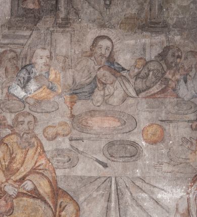 Zdjęcie nr 35: Polichromia pokrywa ściany i sklepienie kolebkowe z lunetami czworobocznej, dwuprzęsłowej zakrystii. Pole sklepienia wypełnia dekoracja ornamentalna utworzona ze zawijanych liści akantu, stylizowanych kwiatów oraz wazonów z kwiatami. Pośrodku sklepienia umieszczono w owalu w kartuszu fragmentarycznie zachowaną scenę Koronacji Marii. W centrum kompozycji zachowała się głowa Marii ujęta w trzy czwarte w prawo z widocznym fragmentem prawego ramienia i ułożonej do modlitwy prawej ręki. Po prawej stronie widać postać tronującego Boga Ojca w złotej koronie, z brodą, trzymającego złotą koronę nad głową Marii. Z lewej można dostrzec fragment ręki Chrystusa oraz fragment jego czerwonej szaty i lewej stopy. Na ścianie wschodniej dekorację malarską w postaci wici utworzonej ze stylizowanych liści akantu i kwiatów poprowadzono w glifie okiennym. Wokół okna utworzono malowane obramienie z motywami stylizowanego ornamentu rollwerkowego. Ponad oknem w glifie znajduje się malowany chrystogram "IHS". Po prawej stronie okna widoczne jest całopostaciowe przedstawienie proroka Eliasza z rozłożonymi rękami. Postać została ujęta w trzech czwartych w prawo. Ma pociągłą twarz okoloną zarostem z wydatnym nosem i ustami. Ubrana jest w strój wschodni - długą szatę z bladoczerwonym płaszczem z kołnierzykiem spiętym przy szyi oraz z rozciętymi rękawami. Na głowie ma szaroniebieski turban. Ponad nim widać lecącego kruka. Obok mężczyzny z prawej strony widoczna jest niewielka sekwencja krajobrazowa z motywem drzewa. Eliasz zwrócony jest w stronę sceny z Ostatnią Wieczerzą wykonaną w pierwszym przęśle ściany południowej zakrystii. Ostatnią Wieczerzę z prawej strony zamyka malowana kolumna z kapitelem rozdzielająca ścianę na dwa przęsła. Na tle altany ze schodami po lewej, flankowanej trzema kolumnami na wysokich cokołach, ukazano Chrystusa i dwunastu apostołów siedzący przy okrągłym, okazałym stole. Ponad stołem wisi płonącą lampa. Stół nakryto białym obrusem zastawionym siedmioma talerzami, owalną misą pośrodku, trzema okrągłymi bochenkami chleba, dwoma nożami i kielichem. Siedzący centralnie za stołem Chrystus został ukazany frontalnie. Zbawiciel ma zmęczoną twarz otoczoną brodą i długimi włosami, spływającymi na ramiona. Ubrany jest w białą tunikę i niebieski płaszcz przerzucony przez lewe ramię. O jego pierś opiera się zamyślony św. Jan, wspierający głowę na prawej ręce trzymanej na stole. Lewą rękę położoną na blacie ma zgiętą w łokciu. Wokół stołu siedzą rozmawiający ze sobą pozostali apostołowie. Są to starsi, brodaci mężczyźni, niektórzy z nich są łysi. Ubrani są w tuniki i narzucone na ramionach płaszcze. Można spośród nich wyróżnić siedzącego po prawe strony Chrystusa św. Piotra oraz Judasza widocznego jako pierwszego po lewej stronie kompozycji. Judasza ukazanego frontalnie identyfikuje żółta szata oraz trzymany w prawej ręce mieszek ze srebnikami. Powyżej w podłuczu lunety namalowano siedzącego, starszego brodatego mężczyznę ujętego w trzech czwartych w prawo. Jest to ewangelista widoczny do kolan. Prawą rękę przyciska do piersi lewą zaś opiera o stół ustawiony z prawej strony kompozycji z ułożoną na nim księgą. Jego twarz charakteryzuje wydatny nos i usta oraz spojrzenie skierowane na widza. W drugim przęśle ściany  
południowej dekoracje tworzy stylizowana wić akantowo-kwiatowa w glifie okiennym oraz otaczające okno obramienie utworzone z motywów rollwerkowych. Nie zachowała się polichromia w lunecie powyżej okna. Na zachodniej ścianie w glifie dawnego otworu wejściowego obramionego żółtą listwą, wykonano dekorację malarską składającą się z malowanych romboidalnych płycin pokrytych czerwonawą marmoryzacją. Ponad glifem na ścianie znajduje się czerwony krzyż równoramienny rozdzielający datę 16 / 46. Na ścianie z prawej strony otworu wyobrażono Ukrzyżowanie Chrystusa na polu pokrytym licznymi, stojącymi krzyżami. Postać Zbawiciela zachowała się fragmentarycznie w partii tułowia i nóg. Powyżej pole w lunecie ozdobiono stylizowaną wicią akantowo-kwiatową. Ścianę północną w pierwszym przęśle wypełnionym szafą zakrystyjną udekorowano rozpostartym, czerwonym paludamentum z baldachimem. Powyżej w lunecie zachowało się bardzo zniszczone przedstawienie św. Jana Ewangelisty, którego można rozpoznać po młodzieńczej, pociągłej twarz o wydatnych rysach. Z postaci zachowały się jeszcze  fragmenty stóp widoczne nad baldachimem. W drugim prześle w dolnej strefie przepruto drzwi z otworem zamkniętym łukiem odcinkowym, obramienionym złocistą taśmą. W nadprożu znalazła się stylizowana wić akantowo-kwiatowa. Powyżej, w górnej strefie namalowano modlitwę Chrystusa w Ogrójcu. Na pierwszym planie kompozycji widoczny jest klęczący na ziemi Zbawiciel ujęty w trzech czwartych w prawo. Lewą rękę ma przyłożoną do piersi, drugą zaś odsuniętą od tułowia. Jego uniesioną głowę ku górze otacza ciemna broda i długie włosy spływające na plecy. Chrystus ma wydatny nos i usta. Ubrany jest w obszerną, jasnooliwkową tunikę przewiązaną w pasie oraz niebieskoszary płaszcz przerzucony przez lewe ramię i rękę. Jezus wpatruje się w zjawiającego mu się powyżej uskrzydlonego anioła ukazanego w dwóch trzecich na obłokach. Anioł w wyciągniętej prawej ręce trzyma złoty kielich, a prawą podtrzymuje opary o ramię krzyż. Ubrany jest w baldoczerwoną tunikę przewiązaną w pasie. Z prawej strony Jezusa widocznych jest trzech śpiących apostołów. Na pierwszym planie ukazano leżącego św. Piotra z głową wspartą na lewej ręce. Jest to starszy mężczyzna z łysym czołem i siwiejącymi włosami i brodą. Ubrany jest w bladoniebieską tunikę i ciemnoochrowy płaszcz. Za nim widać siedzącego św. Jana z głową wspartą na ręce, którą podpiera o prawe kolano. Jest to młodzieniec o długich włosach, ubrany w blado oliwkową tunikę i baldoczerwony płaszcz. O niewielki wzgórek z lewej strony Jana oparty jest św. Jakub. Jest to starszy mężczyzna z brązową brodą i włosami ubrany w bladooliwkowy płaszcz. Za Zbawicielem z lewej strony kompozycji widać drewniany płot z bramką, przez którą do ogrodu wchodzi Judasz w jasno-chórowej szacie, prowadzący zbrojny oddział sług świątynnych. W głębi kompozycji ukazano panoramę Jerozolimy. Powyżej na sklepieniu lunety wyobrażono siedzącego ewangelistę, który ukazany został jako starzec z długą siwą brodą i łysiejącym czołem. Mężczyzna wspierając prawą rękę o stół podpiera nią głowę. Lewą ma położoną na kolanie. Ubrany jest w szarą tunikę oraz bladoczerwony płaszcz przerzucony przez prawe ramię i okrywający kolana.    
