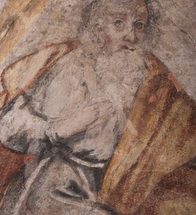 Zdjęcie nr 34: Polichromia pokrywa ściany i sklepienie kolebkowe z lunetami czworobocznej, dwuprzęsłowej zakrystii. Pole sklepienia wypełnia dekoracja ornamentalna utworzona ze zawijanych liści akantu, stylizowanych kwiatów oraz wazonów z kwiatami. Pośrodku sklepienia umieszczono w owalu w kartuszu fragmentarycznie zachowaną scenę Koronacji Marii. W centrum kompozycji zachowała się głowa Marii ujęta w trzy czwarte w prawo z widocznym fragmentem prawego ramienia i ułożonej do modlitwy prawej ręki. Po prawej stronie widać postać tronującego Boga Ojca w złotej koronie, z brodą, trzymającego złotą koronę nad głową Marii. Z lewej można dostrzec fragment ręki Chrystusa oraz fragment jego czerwonej szaty i lewej stopy. Na ścianie wschodniej dekorację malarską w postaci wici utworzonej ze stylizowanych liści akantu i kwiatów poprowadzono w glifie okiennym. Wokół okna utworzono malowane obramienie z motywami stylizowanego ornamentu rollwerkowego. Ponad oknem w glifie znajduje się malowany chrystogram &quot;IHS&quot;. Po prawej stronie okna widoczne jest całopostaciowe przedstawienie proroka Eliasza z rozłożonymi rękami. Postać została ujęta w trzech czwartych w prawo. Ma pociągłą twarz okoloną zarostem z wydatnym nosem i ustami. Ubrana jest w strój wschodni - długą szatę z bladoczerwonym płaszczem z kołnierzykiem spiętym przy szyi oraz z rozciętymi rękawami. Na głowie ma szaroniebieski turban. Ponad nim widać lecącego kruka. Obok mężczyzny z prawej strony widoczna jest niewielka sekwencja krajobrazowa z motywem drzewa. Eliasz zwrócony jest w stronę sceny z Ostatnią Wieczerzą wykonaną w pierwszym przęśle ściany południowej zakrystii. Ostatnią Wieczerzę z prawej strony zamyka malowana kolumna z kapitelem rozdzielająca ścianę na dwa przęsła. Na tle altany ze schodami po lewej, flankowanej trzema kolumnami na wysokich cokołach, ukazano Chrystusa i dwunastu apostołów siedzący przy okrągłym, okazałym stole. Ponad stołem wisi płonącą lampa. Stół nakryto białym obrusem zastawionym siedmioma talerzami, owalną misą pośrodku, trzema okrągłymi bochenkami chleba, dwoma nożami i kielichem. Siedzący centralnie za stołem Chrystus został ukazany frontalnie. Zbawiciel ma zmęczoną twarz otoczoną brodą i długimi włosami, spływającymi na ramiona. Ubrany jest w białą tunikę i niebieski płaszcz przerzucony przez lewe ramię. O jego pierś opiera się zamyślony św. Jan, wspierający głowę na prawej ręce trzymanej na stole. Lewą rękę położoną na blacie ma zgiętą w łokciu. Wokół stołu siedzą rozmawiający ze sobą pozostali apostołowie. Są to starsi, brodaci mężczyźni, niektórzy z nich są łysi. Ubrani są w tuniki i narzucone na ramionach płaszcze. Można spośród nich wyróżnić siedzącego po prawe strony Chrystusa św. Piotra oraz Judasza widocznego jako pierwszego po lewej stronie kompozycji. Judasza ukazanego frontalnie identyfikuje żółta szata oraz trzymany w prawej ręce mieszek ze srebnikami. Powyżej w podłuczu lunety namalowano siedzącego, starszego brodatego mężczyznę ujętego w trzech czwartych w prawo. Jest to ewangelista widoczny do kolan. Prawą rękę przyciska do piersi lewą zaś opiera o stół ustawiony z prawej strony kompozycji z ułożoną na nim księgą. Jego twarz charakteryzuje wydatny nos i usta oraz spojrzenie skierowane na widza. W drugim przęśle ściany  
południowej dekoracje tworzy stylizowana wić akantowo-kwiatowa w glifie okiennym oraz otaczające okno obramienie utworzone z motywów rollwerkowych. Nie zachowała się polichromia w lunecie powyżej okna. Na zachodniej ścianie w glifie dawnego otworu wejściowego obramionego żółtą listwą, wykonano dekorację malarską składającą się z malowanych romboidalnych płycin pokrytych czerwonawą marmoryzacją. Ponad glifem na ścianie znajduje się czerwony krzyż równoramienny rozdzielający datę 16 / 46. Na ścianie z prawej strony otworu wyobrażono Ukrzyżowanie Chrystusa na polu pokrytym licznymi, stojącymi krzyżami. Postać Zbawiciela zachowała się fragmentarycznie w partii tułowia i nóg. Powyżej pole w lunecie ozdobiono stylizowaną wicią akantowo-kwiatową. Ścianę północną w pierwszym przęśle wypełnionym szafą zakrystyjną udekorowano rozpostartym, czerwonym paludamentum z baldachimem. Powyżej w lunecie zachowało się bardzo zniszczone przedstawienie św. Jana Ewangelisty, którego można rozpoznać po młodzieńczej, pociągłej twarz o wydatnych rysach. Z postaci zachowały się jeszcze  fragmenty stóp widoczne nad baldachimem. W drugim prześle w dolnej strefie przepruto drzwi z otworem zamkniętym łukiem odcinkowym, obramienionym złocistą taśmą. W nadprożu znalazła się stylizowana wić akantowo-kwiatowa. Powyżej, w górnej strefie namalowano modlitwę Chrystusa w Ogrójcu. Na pierwszym planie kompozycji widoczny jest klęczący na ziemi Zbawiciel ujęty w trzech czwartych w prawo. Lewą rękę ma przyłożoną do piersi, drugą zaś odsuniętą od tułowia. Jego uniesioną głowę ku górze otacza ciemna broda i długie włosy spływające na plecy. Chrystus ma wydatny nos i usta. Ubrany jest w obszerną, jasnooliwkową tunikę przewiązaną w pasie oraz niebieskoszary płaszcz przerzucony przez lewe ramię i rękę. Jezus wpatruje się w zjawiającego mu się powyżej uskrzydlonego anioła ukazanego w dwóch trzecich na obłokach. Anioł w wyciągniętej prawej ręce trzyma złoty kielich, a prawą podtrzymuje opary o ramię krzyż. Ubrany jest w baldoczerwoną tunikę przewiązaną w pasie. Z prawej strony Jezusa widocznych jest trzech śpiących apostołów. Na pierwszym planie ukazano leżącego św. Piotra z głową wspartą na lewej ręce. Jest to starszy mężczyzna z łysym czołem i siwiejącymi włosami i brodą. Ubrany jest w bladoniebieską tunikę i ciemnoochrowy płaszcz. Za nim widać siedzącego św. Jana z głową wspartą na ręce, którą podpiera o prawe kolano. Jest to młodzieniec o długich włosach, ubrany w blado oliwkową tunikę i baldoczerwony płaszcz. O niewielki wzgórek z lewej strony Jana oparty jest św. Jakub. Jest to starszy mężczyzna z brązową brodą i włosami ubrany w bladooliwkowy płaszcz. Za Zbawicielem z lewej strony kompozycji widać drewniany płot z bramką, przez którą do ogrodu wchodzi Judasz w jasno-chórowej szacie, prowadzący zbrojny oddział sług świątynnych. W głębi kompozycji ukazano panoramę Jerozolimy. Powyżej na sklepieniu lunety wyobrażono siedzącego ewangelistę, który ukazany został jako starzec z długą siwą brodą i łysiejącym czołem. Mężczyzna wspierając prawą rękę o stół podpiera nią głowę. Lewą ma położoną na kolanie. Ubrany jest w szarą tunikę oraz bladoczerwony płaszcz przerzucony przez prawe ramię i okrywający kolana.    
