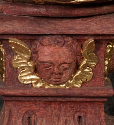 Zdjęcie nr 10: Kamienna chrzcielnica osadzona na wysokim cokole na planie kwadratu, z profilowanym, wielostopniowym trzonem, dekorowanym puklowaniem, liśćmi akantu i uskrzydlonymi główkami anielskimi. Czara puklowana, ozdobiona kartuszem z godłem herbowym Jastrzębiec od frontu oraz kartuszem z godłem herbowym Gryf po przeciwnej stronie, po bokach dwa bukraniony. Chrzcielnica polichromowana w kolorze czerwonym ze złoconymi detalami. Drewniana pokrywa w formie podstawy dekorowanej perełkowaniem i żłobkami, zwieńczona klasycystycznym wazonem zdobionym girlandami, zakończonym kwiatem. 
Chrzcielnica umieszczona w niszy drewnianej oprawy filara arkady tęczowej. Nadbudowa jest architektoniczna, dwukondygnacyjna ze zwieńczeniem. Pierwsza kondygnacja z niszą ujętą dwustrefowym cokołem, zakończonym profilowanym gzymsem dekorowanym żłobkami, zakończonym kartuszem, flankowana kwiatowymi zwisami. Druga kondygnacja z płyciną ujętą pilastrami ozdobionymi kwiatowymi zwisami, zakończonymi gzymsem przechodzącym w woluty, na których znajdują się uskrzydlone główki anielskie. W niszy na rzeźbionym fragmencie skały, flankowanym dwoma drzewami, grupa rzeźbiarska Chrztu Chrystusa. Nad nią na łuku gołębica Ducha Świętego w glorii promienistej. Zwieńczenie w kształcie zbliżonym do kwadratu, ujętego spływami wolutowymi dekorowanymi akantem, zakończone gzymsem i baldachimem. W polu, na obłoku rzeźbiona półpostać Boga Ojca z nimbem trójkątnym i promienistym wokół głowy. Baldachim na planie półkola, w formie niepełnego belkowania, na nim cztery kabłąki podtrzymujące cokół, na którym znajduje się klasycystyczny wazon. Oprawa polichromowana w kolorze seledynowym, ze złoconymi profilami i ornamentyką. 
