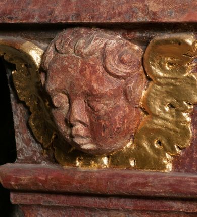 Zdjęcie nr 8: Kamienna chrzcielnica osadzona na wysokim cokole na planie kwadratu, z profilowanym, wielostopniowym trzonem, dekorowanym puklowaniem, liśćmi akantu i uskrzydlonymi główkami anielskimi. Czara puklowana, ozdobiona kartuszem z godłem herbowym Jastrzębiec od frontu oraz kartuszem z godłem herbowym Gryf po przeciwnej stronie, po bokach dwa bukraniony. Chrzcielnica polichromowana w kolorze czerwonym ze złoconymi detalami. Drewniana pokrywa w formie podstawy dekorowanej perełkowaniem i żłobkami, zwieńczona klasycystycznym wazonem zdobionym girlandami, zakończonym kwiatem. 
Chrzcielnica umieszczona w niszy drewnianej oprawy filara arkady tęczowej. Nadbudowa jest architektoniczna, dwukondygnacyjna ze zwieńczeniem. Pierwsza kondygnacja z niszą ujętą dwustrefowym cokołem, zakończonym profilowanym gzymsem dekorowanym żłobkami, zakończonym kartuszem, flankowana kwiatowymi zwisami. Druga kondygnacja z płyciną ujętą pilastrami ozdobionymi kwiatowymi zwisami, zakończonymi gzymsem przechodzącym w woluty, na których znajdują się uskrzydlone główki anielskie. W niszy na rzeźbionym fragmencie skały, flankowanym dwoma drzewami, grupa rzeźbiarska Chrztu Chrystusa. Nad nią na łuku gołębica Ducha Świętego w glorii promienistej. Zwieńczenie w kształcie zbliżonym do kwadratu, ujętego spływami wolutowymi dekorowanymi akantem, zakończone gzymsem i baldachimem. W polu, na obłoku rzeźbiona półpostać Boga Ojca z nimbem trójkątnym i promienistym wokół głowy. Baldachim na planie półkola, w formie niepełnego belkowania, na nim cztery kabłąki podtrzymujące cokół, na którym znajduje się klasycystyczny wazon. Oprawa polichromowana w kolorze seledynowym, ze złoconymi profilami i ornamentyką. 
