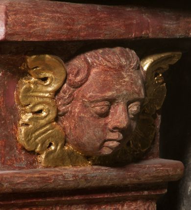 Zdjęcie nr 7: Kamienna chrzcielnica osadzona na wysokim cokole na planie kwadratu, z profilowanym, wielostopniowym trzonem, dekorowanym puklowaniem, liśćmi akantu i uskrzydlonymi główkami anielskimi. Czara puklowana, ozdobiona kartuszem z godłem herbowym Jastrzębiec od frontu oraz kartuszem z godłem herbowym Gryf po przeciwnej stronie, po bokach dwa bukraniony. Chrzcielnica polichromowana w kolorze czerwonym ze złoconymi detalami. Drewniana pokrywa w formie podstawy dekorowanej perełkowaniem i żłobkami, zwieńczona klasycystycznym wazonem zdobionym girlandami, zakończonym kwiatem. 
Chrzcielnica umieszczona w niszy drewnianej oprawy filara arkady tęczowej. Nadbudowa jest architektoniczna, dwukondygnacyjna ze zwieńczeniem. Pierwsza kondygnacja z niszą ujętą dwustrefowym cokołem, zakończonym profilowanym gzymsem dekorowanym żłobkami, zakończonym kartuszem, flankowana kwiatowymi zwisami. Druga kondygnacja z płyciną ujętą pilastrami ozdobionymi kwiatowymi zwisami, zakończonymi gzymsem przechodzącym w woluty, na których znajdują się uskrzydlone główki anielskie. W niszy na rzeźbionym fragmencie skały, flankowanym dwoma drzewami, grupa rzeźbiarska Chrztu Chrystusa. Nad nią na łuku gołębica Ducha Świętego w glorii promienistej. Zwieńczenie w kształcie zbliżonym do kwadratu, ujętego spływami wolutowymi dekorowanymi akantem, zakończone gzymsem i baldachimem. W polu, na obłoku rzeźbiona półpostać Boga Ojca z nimbem trójkątnym i promienistym wokół głowy. Baldachim na planie półkola, w formie niepełnego belkowania, na nim cztery kabłąki podtrzymujące cokół, na którym znajduje się klasycystyczny wazon. Oprawa polichromowana w kolorze seledynowym, ze złoconymi profilami i ornamentyką. 
