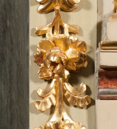 Zdjęcie nr 19: Kamienna chrzcielnica osadzona na wysokim cokole na planie kwadratu, z profilowanym, wielostopniowym trzonem, dekorowanym puklowaniem, liśćmi akantu i uskrzydlonymi główkami anielskimi. Czara puklowana, ozdobiona kartuszem z godłem herbowym Jastrzębiec od frontu oraz kartuszem z godłem herbowym Gryf po przeciwnej stronie, po bokach dwa bukraniony. Chrzcielnica polichromowana w kolorze czerwonym ze złoconymi detalami. Drewniana pokrywa w formie podstawy dekorowanej perełkowaniem i żłobkami, zwieńczona klasycystycznym wazonem zdobionym girlandami, zakończonym kwiatem. 
Chrzcielnica umieszczona w niszy drewnianej oprawy filara arkady tęczowej. Nadbudowa jest architektoniczna, dwukondygnacyjna ze zwieńczeniem. Pierwsza kondygnacja z niszą ujętą dwustrefowym cokołem, zakończonym profilowanym gzymsem dekorowanym żłobkami, zakończonym kartuszem, flankowana kwiatowymi zwisami. Druga kondygnacja z płyciną ujętą pilastrami ozdobionymi kwiatowymi zwisami, zakończonymi gzymsem przechodzącym w woluty, na których znajdują się uskrzydlone główki anielskie. W niszy na rzeźbionym fragmencie skały, flankowanym dwoma drzewami, grupa rzeźbiarska Chrztu Chrystusa. Nad nią na łuku gołębica Ducha Świętego w glorii promienistej. Zwieńczenie w kształcie zbliżonym do kwadratu, ujętego spływami wolutowymi dekorowanymi akantem, zakończone gzymsem i baldachimem. W polu, na obłoku rzeźbiona półpostać Boga Ojca z nimbem trójkątnym i promienistym wokół głowy. Baldachim na planie półkola, w formie niepełnego belkowania, na nim cztery kabłąki podtrzymujące cokół, na którym znajduje się klasycystyczny wazon. Oprawa polichromowana w kolorze seledynowym, ze złoconymi profilami i ornamentyką. 
