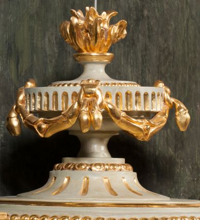 Zdjęcie nr 15: Kamienna chrzcielnica osadzona na wysokim cokole na planie kwadratu, z profilowanym, wielostopniowym trzonem, dekorowanym puklowaniem, liśćmi akantu i uskrzydlonymi główkami anielskimi. Czara puklowana, ozdobiona kartuszem z godłem herbowym Jastrzębiec od frontu oraz kartuszem z godłem herbowym Gryf po przeciwnej stronie, po bokach dwa bukraniony. Chrzcielnica polichromowana w kolorze czerwonym ze złoconymi detalami. Drewniana pokrywa w formie podstawy dekorowanej perełkowaniem i żłobkami, zwieńczona klasycystycznym wazonem zdobionym girlandami, zakończonym kwiatem. 
Chrzcielnica umieszczona w niszy drewnianej oprawy filara arkady tęczowej. Nadbudowa jest architektoniczna, dwukondygnacyjna ze zwieńczeniem. Pierwsza kondygnacja z niszą ujętą dwustrefowym cokołem, zakończonym profilowanym gzymsem dekorowanym żłobkami, zakończonym kartuszem, flankowana kwiatowymi zwisami. Druga kondygnacja z płyciną ujętą pilastrami ozdobionymi kwiatowymi zwisami, zakończonymi gzymsem przechodzącym w woluty, na których znajdują się uskrzydlone główki anielskie. W niszy na rzeźbionym fragmencie skały, flankowanym dwoma drzewami, grupa rzeźbiarska Chrztu Chrystusa. Nad nią na łuku gołębica Ducha Świętego w glorii promienistej. Zwieńczenie w kształcie zbliżonym do kwadratu, ujętego spływami wolutowymi dekorowanymi akantem, zakończone gzymsem i baldachimem. W polu, na obłoku rzeźbiona półpostać Boga Ojca z nimbem trójkątnym i promienistym wokół głowy. Baldachim na planie półkola, w formie niepełnego belkowania, na nim cztery kabłąki podtrzymujące cokół, na którym znajduje się klasycystyczny wazon. Oprawa polichromowana w kolorze seledynowym, ze złoconymi profilami i ornamentyką. 
