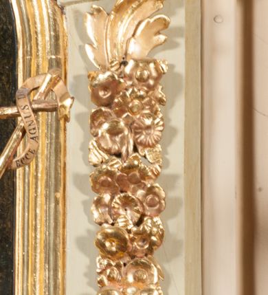 Zdjęcie nr 20: Kamienna chrzcielnica osadzona na wysokim cokole na planie kwadratu, z profilowanym, wielostopniowym trzonem, dekorowanym puklowaniem, liśćmi akantu i uskrzydlonymi główkami anielskimi. Czara puklowana, ozdobiona kartuszem z godłem herbowym Jastrzębiec od frontu oraz kartuszem z godłem herbowym Gryf po przeciwnej stronie, po bokach dwa bukraniony. Chrzcielnica polichromowana w kolorze czerwonym ze złoconymi detalami. Drewniana pokrywa w formie podstawy dekorowanej perełkowaniem i żłobkami, zwieńczona klasycystycznym wazonem zdobionym girlandami, zakończonym kwiatem. 
Chrzcielnica umieszczona w niszy drewnianej oprawy filara arkady tęczowej. Nadbudowa jest architektoniczna, dwukondygnacyjna ze zwieńczeniem. Pierwsza kondygnacja z niszą ujętą dwustrefowym cokołem, zakończonym profilowanym gzymsem dekorowanym żłobkami, zakończonym kartuszem, flankowana kwiatowymi zwisami. Druga kondygnacja z płyciną ujętą pilastrami ozdobionymi kwiatowymi zwisami, zakończonymi gzymsem przechodzącym w woluty, na których znajdują się uskrzydlone główki anielskie. W niszy na rzeźbionym fragmencie skały, flankowanym dwoma drzewami, grupa rzeźbiarska Chrztu Chrystusa. Nad nią na łuku gołębica Ducha Świętego w glorii promienistej. Zwieńczenie w kształcie zbliżonym do kwadratu, ujętego spływami wolutowymi dekorowanymi akantem, zakończone gzymsem i baldachimem. W polu, na obłoku rzeźbiona półpostać Boga Ojca z nimbem trójkątnym i promienistym wokół głowy. Baldachim na planie półkola, w formie niepełnego belkowania, na nim cztery kabłąki podtrzymujące cokół, na którym znajduje się klasycystyczny wazon. Oprawa polichromowana w kolorze seledynowym, ze złoconymi profilami i ornamentyką. 
