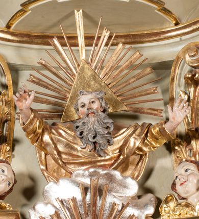 Zdjęcie nr 37: Kamienna chrzcielnica osadzona na wysokim cokole na planie kwadratu, z profilowanym, wielostopniowym trzonem, dekorowanym puklowaniem, liśćmi akantu i uskrzydlonymi główkami anielskimi. Czara puklowana, ozdobiona kartuszem z godłem herbowym Jastrzębiec od frontu oraz kartuszem z godłem herbowym Gryf po przeciwnej stronie, po bokach dwa bukraniony. Chrzcielnica polichromowana w kolorze czerwonym ze złoconymi detalami. Drewniana pokrywa w formie podstawy dekorowanej perełkowaniem i żłobkami, zwieńczona klasycystycznym wazonem zdobionym girlandami, zakończonym kwiatem. 
Chrzcielnica umieszczona w niszy drewnianej oprawy filara arkady tęczowej. Nadbudowa jest architektoniczna, dwukondygnacyjna ze zwieńczeniem. Pierwsza kondygnacja z niszą ujętą dwustrefowym cokołem, zakończonym profilowanym gzymsem dekorowanym żłobkami, zakończonym kartuszem, flankowana kwiatowymi zwisami. Druga kondygnacja z płyciną ujętą pilastrami ozdobionymi kwiatowymi zwisami, zakończonymi gzymsem przechodzącym w woluty, na których znajdują się uskrzydlone główki anielskie. W niszy na rzeźbionym fragmencie skały, flankowanym dwoma drzewami, grupa rzeźbiarska Chrztu Chrystusa. Nad nią na łuku gołębica Ducha Świętego w glorii promienistej. Zwieńczenie w kształcie zbliżonym do kwadratu, ujętego spływami wolutowymi dekorowanymi akantem, zakończone gzymsem i baldachimem. W polu, na obłoku rzeźbiona półpostać Boga Ojca z nimbem trójkątnym i promienistym wokół głowy. Baldachim na planie półkola, w formie niepełnego belkowania, na nim cztery kabłąki podtrzymujące cokół, na którym znajduje się klasycystyczny wazon. Oprawa polichromowana w kolorze seledynowym, ze złoconymi profilami i ornamentyką. 
