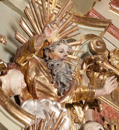 Zdjęcie nr 36: Kamienna chrzcielnica osadzona na wysokim cokole na planie kwadratu, z profilowanym, wielostopniowym trzonem, dekorowanym puklowaniem, liśćmi akantu i uskrzydlonymi główkami anielskimi. Czara puklowana, ozdobiona kartuszem z godłem herbowym Jastrzębiec od frontu oraz kartuszem z godłem herbowym Gryf po przeciwnej stronie, po bokach dwa bukraniony. Chrzcielnica polichromowana w kolorze czerwonym ze złoconymi detalami. Drewniana pokrywa w formie podstawy dekorowanej perełkowaniem i żłobkami, zwieńczona klasycystycznym wazonem zdobionym girlandami, zakończonym kwiatem. 
Chrzcielnica umieszczona w niszy drewnianej oprawy filara arkady tęczowej. Nadbudowa jest architektoniczna, dwukondygnacyjna ze zwieńczeniem. Pierwsza kondygnacja z niszą ujętą dwustrefowym cokołem, zakończonym profilowanym gzymsem dekorowanym żłobkami, zakończonym kartuszem, flankowana kwiatowymi zwisami. Druga kondygnacja z płyciną ujętą pilastrami ozdobionymi kwiatowymi zwisami, zakończonymi gzymsem przechodzącym w woluty, na których znajdują się uskrzydlone główki anielskie. W niszy na rzeźbionym fragmencie skały, flankowanym dwoma drzewami, grupa rzeźbiarska Chrztu Chrystusa. Nad nią na łuku gołębica Ducha Świętego w glorii promienistej. Zwieńczenie w kształcie zbliżonym do kwadratu, ujętego spływami wolutowymi dekorowanymi akantem, zakończone gzymsem i baldachimem. W polu, na obłoku rzeźbiona półpostać Boga Ojca z nimbem trójkątnym i promienistym wokół głowy. Baldachim na planie półkola, w formie niepełnego belkowania, na nim cztery kabłąki podtrzymujące cokół, na którym znajduje się klasycystyczny wazon. Oprawa polichromowana w kolorze seledynowym, ze złoconymi profilami i ornamentyką. 
