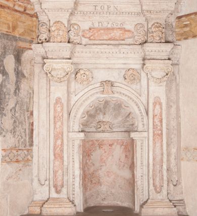 Zdjęcie nr 1: Kamienny lawetarz został osadzony na cokole, którego front zdobi putto trzymające w ręce kartusz herbowy z nieczytelnym godłem. Pod kartuszem widoczna jest czworoboczna wnęka. Nad cokołem znajduje się nisza konchowa z konchą wypełnioną muszlą, ujęta jońskimi pilastrami podtrzymującymi belkowanie, którego fryz ozdobiono główkami aniołków. Archiwolta ponad konchą została na środku przewiązana wolutowym kluczem. Z kolei w przyłuczu konchy znalazły się dwie rozety. Kapitele pilastrów flankujące niszę dodatkowo dekorowane są podwieszonymi girlandami, zaś ich trzony wydłużonymi płycinami. Architraw i gzyms zdobione są kostkowaniem. Na belkowaniu widnieje inskrypcja: „T(HOMAS) O(LINSKI) P(LEBANUS) N(IEPOLOMICENSIS) / A(NNO) D(OMINI) 1696”. Całość wieńczy figura diakona ubranego w białą albę i pomarańczową dalmatykę. W lewej ręce trzyma zamkniętą księgę. Prawa ręka uniesiona na wysokości pasa jest uszkodzona.