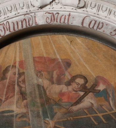 Zdjęcie nr 7: Obraz uzyskał kształt stojącego prostokąta zamkniętego łukiem pełnym. W pomieszczeniu o szarych ścianach, ukazano scenę narodzin św. Karola Boromeusza. Komnata otwiera sie z lewej strony na schematycznie przedstawiony pagórkowaty pejzaż. Wewnątrz na ukośnie ułożonym łożu, spoczywa matka świętego, trzymając ugięte w łokciach ręce na wysokości pasa. Łoże posiada zaplecek o fantazyjnym wykroju, a ponad nim widać podwieszoną u góry czerwoną kotarę. Leżąca kobieta ma owalną twarz o jasnej karnacji, okoloną jasnobrązowymi włosami opadającymi na ramiona. Ubrana jest w białą koszulę z długimi rękawami oraz czepiec na głowie. Za łożem po lewej stronie widoczna jest służąca podtrzymująca obiema rękami swą Panią. Niewiasta ubrana jest w jasnoniebieską suknię oraz białą chustę zakrywającą włosy. Przed łożem została ukazana położna owijająca w pieluszkę noworodka. Robi to na stole nakrytym niebieską tkaniną. Kobieta ubrana jest w białą koszulę z czerwonym gorsetem, zieloną spódnicę oraz biały fartuch i chustę na głowie. Niemowlę jest nagie. Wyciągając przed siebie rączki leży ukośnie na ramionach służki. Jego głowę okala świetlisty nimb. Za nim widoczna jest głowa przyglądającej sie scenie dziewczynki. Po prawej stronie łoża ukazany został zasiadąjacy na zielonym fotelu o wysokim zaplecku ojciec Karola Boromeusza. Mężczyzna zwrócony jest w trzech czwartych w lewo. Prawą dłoń przyciska do piersi, lewą ugiętą w łokciu wyciąga przed siebie. Ma twarz o brunatnoszarej karnacji okolonej długą, rozdwojoną na końcach brodą. Postać ubrana jest w zieloną szatę oraz czerwony płaszcz i czapkę podbitą futrem. Na pierwszym planie, po prawej stronie, przedstawiono przyklękającą służącą, która zaściela kołyskę. Jest zwrócona w trzech czwartych w lewo z głową silnie odchyloną do tyłu. Ma na sobie czerwoną spódnicę, białą koszulę z żółtym gorsetem, fartuch oraz biało czerwoną chustę na głowie. W górze, nad całą kompozycją widoczna jest grupa aniołów, ukazanych na obłokach do pasa. W rękach trzymają tradycyjne atrybuty św. Karola Boromeusza: krzyż arcybiskupi, pastorał, stułę, infułę oraz krzyż. Na krawędzi archiwolty widnieje czerwony napis łaciński: Vos estis lux Mundi Mat[theus]: Cap[ut]: 5 vers[us]: 14. Napis polski także pisany na czerwono znajduje się na dolnej krawędzi niszy: Światło niebieskie sprzyja gdy się Karol rodzi / wszak piekielny cień cnocie nigdy nie zaszkodzi.