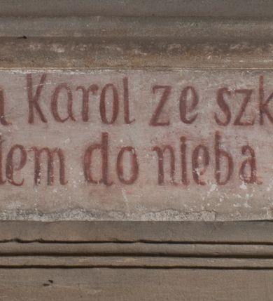 Zdjęcie nr 7: Obraz uzyskał kształt stojącego prostokąta zamkniętego łukiem pełnym. Na tle komnaty o brązowych ścianach, z widoczną po prawej stronie arkadą otwierającą się na kolejne pomieszczenie, ukazany został św. Karol Boromeusz rozdający jałmużnę ubogim. Świętego przedstawiono w całej postaci, zwróconego w trzech czwartych w prawo. Lewą ręką sięga po pieniądze z zielonej szkatuły leżącej na stole obok, prawą natomiast wyciąga w kierunku ubogich. Ze szkatuły wysuwa się purpurowa chusta. Święty Karol Boromeusz ma owalną twarz o prostym nosie, lekko uśmiechniętych ustach, półprzymkniętych oczach, okoloną ciemnobrązowymi, krótkimi włosami. Ubrany jest w strój kardynalski: purpurową sutannę, mucet i piuskę oraz białą komżę. Jego głowę otacza świetlisty nimb. Po jego lewej stronie widoczny jest stół, przykryty sięgającym ziemi białym obrusem ze złotymi frędzlami. Ustawiono na nim drewniany krucyfiks, księgę oraz wspomnianą zieloną szkatułę. Za postacią świętego widoczny jest ozdobny fotel o wysokim zaplecku z zielonym obiciem. Po prawej stronie świętego w wejściu do komnaty przedstawiono w całej postaci żebraków. Pierwszy mężczyzna zwrócony jest profilem w lewo. Wyciąga prawą rękę po pieniądze podawane mu przez świętego, wspierając się lewą dłonią na kosturze. Ma twarz o ciemnobrązowej karnacji, okoloną ciemną, długą brodą. Głowę ma przewiązaną białą chustą. Postać ubrana jest w brunatną tunikę sięgającą kolan oraz czarne buty. Drugi mężczyzna, wspierający się na kosturze, zwrócony jest w trzech czwartych w lewo. Niewidoczna jest jego lewa ręka. Lewą nogę ma uciętą poniżej kolana i zabandażowaną. Powyżej kolana ma owiniętą białym opatrunkiem prawą nogę. Jego twarz jest owalna o ciemnobrązowej karnacji. Przedstawiony został boso w grynszpanowej tunice przewiązanej w pasie i sięgającej kolan, odsłaniającej prawe ramię. Powyżej sceny namalowano podwieszoną, złoto-umbrową kotarę ze złotymi frędzlami.
Ponad obrazem na archiwolcie arkady znajduje się czerwony łaciński napis: „Qui aurum diligit, non iustisificabitur Eccles[iastes] Cap[ut] 31 vers[us] 5”. Natomiast na dolnej krawędzi wnęki napis polski, także wykonany rubrą: „Złoto ubogim Karol ze szkatuły daye / znać ze złotem do nieba nikt się nie dostaye”.