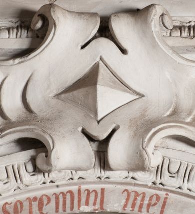 Zdjęcie nr 3: Obraz uzyskał kształt leżącego prostokąta. We wnętrzu pomieszczenia o szarych ścianach ukazano scenę wskrzeszenia Piotrowina przez św. Stanisława ze Szczepanowa. Z lewej strony pomieszczenie otwiera się na rozpościerający się w głębi schematyczny pejzaż z motywem nachodzących na siebie wzgórz. Pośrodku przedstawiono w dwóch trzecich św. Stanisława, zwróconego w trzech czwartych w prawo. Święty w geście błogosławieństwa unosi prawą rękę nad wychylającym się w półpostaci z grobu Piotrowinem. W lewej ręce trzyma złoty pastorał zakończony wolutową krzywaśnią z motywem skręcającej się ulistnionej gałęzi. Jego twarz ma beżowo-szarawą karnację. Charakteryzują ją okrągłe i pełne policzki, wydatny nos, ciemnoczerwone usta i półprzymknięte powiekami oczy. Głowę biskupa okala świetlisty nimb. Święty jest ubrany w strój pontyfikalny – fioletowo-szarą sutannę, białą komżę, na której widać czarny mucet i złocistoczerwoną stułę. Na ramionach ma założoną czerwoną kapę podbitą zgniłozieloną tkaniną i lamowaną złotym obszyciem, a na głowie czerwonozłocistą infułę. Poniżej, z prawej strony św. Stanisława ukazany został do pasa, ze złożonymi w geście modlitwy dłońmi Piotrowin, wychylający się z prostokątnego grobu. Jego twarz ma szarobrunatną karnację. Na kościstej twarzy widać szeroko otwarte oczy i wydatny nos oraz usta okolone ciemnobrązowym zarostem. Piotrowin jest nagi, z założonym na głowę całunem spływającym na ramiona i plecy. Stanisławowi towarzyszą trzy postacie stojące po jego lewej stronie. Pierwszą jest duchowny zwrócony w trzech czwartych w prawo z lekko ugiętą w łokciu lewą ręką. Prawą trzyma na wysokości piersi. Ma owalną twarz z wydatnym czołem, szerokim nosem, ciemnymi oczami, wąskimi ustami, okoloną jasnobrązowymi włosami skręcającymi się w pukle. Ubrany jest w strój kanonicki – czarno-szarą sutannę, mucet i piuskę na głowie oraz białą komżę. Obok, z lewej strony ukazani zostali dwaj mężczyźni, z których pierwszy ujęty w całej postaci, zwrócony w trzech czwartych w prawo z lewą ręką przyciśniętą do piersi, ma na sobie szlachecki kontusz. Jego twarz jest owalna i ma zniekształcone rysy. Dominuje duże czoło i szeroki nos oraz czarne oczy i wydatne usta. Ma krótkie ciemnobrązowe włosy zaczesane w grzywkę. Stojący obok drugi mężczyzna widoczny jest tylko częściowo. Ukazany został z profilu z głową zwróconą w prawo. Ma zakrzywiony nos, ciemne oczy i duże, czerwone usta. Widoczny tylko fragmentarycznie strój jest koloru jasnobrązowego. W lewym, górnym rogu obrazu znajdują się złote promienie wyłaniające się z chmur, padające na postać św. Stanisława.