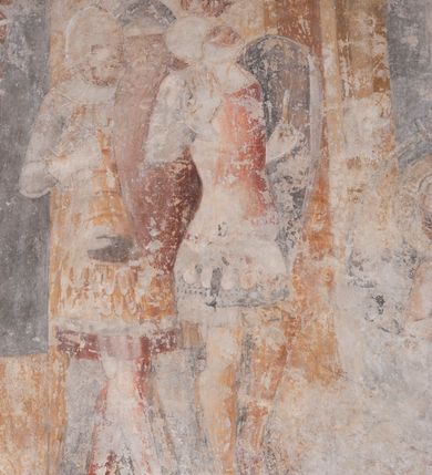 Zdjęcie nr 11: Zachowana dekoracja malarska znajduje się w tzw. starej zakrystii, określanej także jako oratorium królewskie. Dobudowano ją od północy do prezbiterium niepołomickiego kościoła. Jest to niewielka budowla na rzucie wydłużonego prostokąta, nakryta trójprzęsłowym krzyżowo-żebrowym sklepieniem, od wschodu zamknięta dwubocznie. Od zachodu w narożniku południowym widoczne jest załamanie muru, tworzącego dwie ściany wieżyczki schodowej. Do jej wnętrza prowadzi ostrołukowy portal. Oratorium oświetlają trzy ostrołukowe okna. Tylko czwarte, obecnie zamurowane, przeprute w murze północno-wschodnim pochodzi z czasów budowy kościoła. Stara zakrystia połączona jest z kościołem za pomocą ostrołukowego, profilowanego kamiennego portalu umieszczonego w środkowym przęśle ściany południowej. Na sklepieniu znajdują się rzeźbione zworniki z przedstawieniem w przęśle wschodnim głowy Chrystusa w nimbie krzyżowym, w środkowym maski liściastej, a w zachodnim motywów roślinnych. Podobnie rzeźbione motywy roślinne  pokrywają wsporniki, na które spływają żebra. 
Zachowana polichromia tworzy z architekturą starej zakrystii harmonijną całość. Białe wysklepki sklepień otoczone są wielobarwnymi, namalowanymi wzdłuż żeber, iluzjonistyczno-geometrycznymi pasami imitującymi kamienne inkrustacje w typie &quot;arte cosmatesca&quot;. Pierwotnie polichromowane były także same żebra oraz rzeźbione zworniki i wsporniki. Pionowym rytmom barwnych pasów przeciwstawiają się na ścianie wschodniej, południowej i zachodniej dwa poziome, iluzjonistyczne malowane fryzy. Górny, w odcieniach brązów jest szerszy i przypomina gzyms. Przebiega w połowie wysokości ścian, na poziomie wsporników. Poniżej znajduje się drugi, o połowę węższy, skomponowany z wielobarwnych geometrycznych rozet w rombowych polach. Fryzy wyznaczają trzy strefy dekoracji. Dolny pas uległ zniszczeniu za wyjątkiem niewielkiego fragmentu iluzjonistycznie malowanej konsolki na ścianie południowej. Dla strefy środkowej głównej tło stanowi niebieska barwa. Niestety oba te pasy obecnie są mocno uszkodzone. 
Pierwotnie pas środkowy ścian zajmowały naturalnej wielkości postacie kobiece, ujęte powyżej kolan. Z namalowanych dwunastu świętych do naszych czasów przetrwało sześć - w całości cztery (na ścianie wschodniej, południowej i zachodniej) oraz jedna bez głowy (ściana południowa) i jedna w połowie (ściana zachodnia). Są to jasno lub ciemnowłose młode kobiety, trzymające palmy męczeństwa. Ubrane są w suknie z narzuconymi płaszczami w kolorach żółtym, oliwkowym, różowym, liliowym, brązowym i błękitnym. Jedna z nich, wyobrażona ponad wejściem na klatkę schodową w wieżyczce, jest ukazana jako kobieta w podeszłym wieku z okrytą głową i dłońmi uniesionymi na wysokość piersi w geście orantki. Głowy męczennic i orantki okalają plastycznie, tłoczone w zaprawie nimby zdobione promieniami. Na niektórych głowach dziewic zachowały się ślady namalowanych brązową farbą koron o niskich sterczynach w kształcie heraldycznych lilii. 
W ścianie północno-wschodniej dwubocznego zamknięcia znajduje się obecnie zamurowane lancetowate, ostrołukowe okno z fragmentami polichromii w glifie okiennym. Pierwotnie tworzyło ją dziesięć czterolistnych obramowań wpisanych w romby, umieszczonych jeden nad drugim. Przedstawiono w nich w półpostaci aniołów z głowami otoczonymi nimbami. W dolnej części okno do  poziomu gotyckich wsporników otacza iluzjonistycznie malowana dekoracja utworzona z motywów kamiennych płyt.  
W górnej strefie oratorium wyobrażono cykl hagiograficzny, składający się z sześciu scen namalowanych w ostrołukowych polach, wyznaczonych łukami tarczowymi sklepień i ujętych w obramienia z plastycznie malowanych zębów. Ograniczający je od dołu, iluzjonistycznie malowany, jakby wystający gzyms nadaje przedstawieniom teatralną głębie. 
Na ścianie południowo-wschodniej przedstawiono bliżej niezidentyfikowaną scenę męczeństwa. Na tle ochrowo-żółtej architektury ukazano z lewej strony na pierwszym planie grupę  rycerzy, z których dwóch widocznych jest w całej postaci w średniowiecznych zbrojach stylizowanych na rzymskie, w hełmach i z ostrołukowymi tarczami trzymanymi w lewych rękach. Ich odzież ma kolor błękitny, granatowy, czerwony, fioletowy, cynobrowy. Rycerze lekko unoszą głowy w stronę półpostaci wychylającej się z okna loggi w górnej części architektury. Był to zapewne władca, dziś jego postać zachowała się tylko fragmentarycznie. Postać z okna wskazuje palcem na centralnie ukazany kocioł zawieszony pod arkadą, stanowiącą część architektury tła. Widoczna w nim jest w półpostaci jasnowłosa kobieta w białej sukni na ramiączkach z modlitewnie złożonymi rękami na piersi. Jej głowę otacza nimb. Kocioł wisi na haku za półokrągły uchwyt, pod nim pali się ognisko. Z prawej strony kotła widoczna jest fragmentarycznie zachowana postać rycerza w zbroi, który oburącz długim kijem miesza w kotle. 
Na prawo od sceny męczeństwa na ścianie południowej namalowano scenę określaną jako &quot;przed władcą&quot;. W centrum przedstawienia na tle architektury wyobrażono tron z zasiadającym na nim władcą. Jest to brodaty mężczyzna ukazany z profilu z koroną na głowie, który w prawej dłoni unosi berło skierowane w stronę przyprowadzonej do niego kobiety. Tron i architektoniczne jego obramienie malowane jest w kolorach brązu i ochry. Jego zaplecek dekoruje zawieszona pasiasta tkanina. Ciemnowłosy władca ubrany jest w turkusową szatę z narzuconym na ramiona brązowym płaszczem. Za tronem z lewej strony stoi paź o kędzierzawej fryzurze wsparty na trzymanym ostrzem w dół mieczu. Stojąca przed władcą kobieta ubrana jest w czerwoną długą suknię. Ma jasne włosy, a jej głowę okala nimb. Ręce ma skrzyżowane i związane na wysokości pasa. Obok niej stoi inna postać także w długiej szacie, z uniesioną prawą dłonią. Za świętą widoczne są inne postacie, niestety skala zniszczenia malowidła uniemożliwia ich opis i identyfikację. 
Trzecie malowidło, usytuowane nad wejściem do oratorium, ukazuje scenę dysputyt. W centrum przedstawienia pod architektonicznym zadaszeniem w formie portyku lub altany o kasetonowym stropie, wspartym na dwóch czworobocznych filarach, ukazano widoczne z profilu trzy siedzące  kobiety. Jedna z lewej strony a dwie naprzeciwko z prawej. Kobieta z lewej  ma odkryte jasne, długie włosy. Jej głowę otacza nimb. Na wysokość piersi unosi obie dłonie, sprawiając wrażenie, jakby w nich trzymała owalny przedmiot. Ubrana jest w ciemnoczerwoną długą suknię, zakrywającą nogi. Naprzeciw niej siedzą dwie inne niewiasty o długich, jasnych włosach w prostych koronach na głowach. Jedna z nich unosi swoją prawą rękę. Obie ubrane są w długie suknie w kolorze ochry. Za nimi pomiędzy filarami widoczna jest rozpięta zasłona w pionowe oliwkowe, zielone, białe i czerwone pasy. Na podłodze leży dywan dekorowany w żółte, zielone, niebieskie i czerwone pasy. 
Mocno zniszczone w dolnej części czwarte przedstawienie ilustruje scenę chłosty. Z lewej strony kompozycji wyobrażono budowlę z architektoniczną loggią, z której w półpostaci wychyla się władca. W prawej ręce poziomo trzyma berło skierowane w stronę grupy osób, za którymi wykonywana jest kara chłosty. Władca, podobnie jak w drugiej scenie, został ukazany jako mężczyzna o ciemnym zaroście i takich samych włosach. Na głowie ma koronę. Ubrany jest w brązowe szaty o różnych odcieniach. Centralnie przedstawioną stłoczoną grupę tworzy czterech żołnierzy oraz starszy mężczyzna w zawoju na głowie z siwą, długą brodą. Żołnierze mają zbroje i hełmy. Jeden z nich, najbliżej stojący z lewej przedstawiony został w profilu z głową i prawą ręką skierowaną w stronę króla. Także w stronę władcy zwrócony jest mężczyzna w zawoju na głowie z dwiema dłońmi uniesionymi na wysokość piersi. Z prawej strony kompozycji namalowano, dziś fragmentarycznie zachowany, rodzaj drewnianej szubienicy, utworzonej z poprzecznie zawieszonego na drewnianych podporach drążka. Nad dróżką do góry nogami wisi postać (dziś zniszczona), z której zachowały się jedynie stopy związane w kostkach sznurem. W jej stronę zwraca się jeden z żołnierzy ze środkowej grupy. Po prawej stronie szubienicy widoczna jest część postaci oprawcy, z której zachował się tylko fragment głowy oraz uniesiona lewa ręka z drewnianą pałką. 
Dwie ostatnie sceny umieszczono na zachodnim murze oratorium. Pierwsza z nich przedstawia strącenie bożka i została połączona z drugą ukazującą uwolnienia z więzienia. Część centralną kompozycji stanowi potrzaskana, wywracająca się kolumna, z której spada szatan w postaci żywego demona pokrytego sierścią. Strącił go widoczny w półpostaci w górnej części malowidła anioł trzymający w prawej ręce miecz. Z lewej strony kompozycji  klęczy na skalistej ziemi święta ubrana w długą ciemnoczerwoną suknię. Niestety nie zachowała się górna część jej postaci. Za nią stoi stłoczona grupa przerażonych świadków tego wydarzenia. Natomiast z prawej strony malowidła wyobrażono scenę uwolnienia z więzienia. Jej zasadniczym elementem jest architektoniczna struktura nawiązująca kształtem do wieży mieszkalnej, więzienia bądź bramy miejskiej. Święta ze związanymi rękami w ciemnoczerwonej sukni wychodzi z niej z prawej strony. W centrum budowli widoczne jest półokrągłe okno, a w nim zapewne jej popiersie o długich jasnych włosach, trzymające w dłoniach jakiś przedmiot. Wszystkie sceny cyklu w jedną całość wiąże gładkie niebieskie tło. Niezachowana kompozycja polichromii na ścianie północnej musiała odbiegać swym układem od pozostałych ścian. Płaszczyzna ścian została podzielona za pomocą węższego dolnego fryzu na dwie strefy. Górną część najprawdopodobniej zajmowały duże postacie stojące (fragment jednej z nich zachował się w sąsiedztwie okna w ścianie północno-wschodniej). Pod fryzem w części dolnej najprawdopodobniej była namalowana iluzjonistycznie wisząca kotara.   
    




