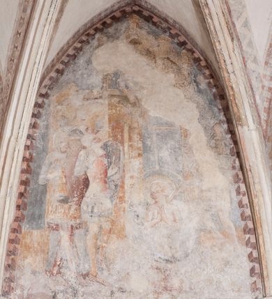 Zdjęcie nr 12: Zachowana dekoracja malarska znajduje się w tzw. starej zakrystii, określanej także jako oratorium królewskie. Dobudowano ją od północy do prezbiterium niepołomickiego kościoła. Jest to niewielka budowla na rzucie wydłużonego prostokąta, nakryta trójprzęsłowym krzyżowo-żebrowym sklepieniem, od wschodu zamknięta dwubocznie. Od zachodu w narożniku południowym widoczne jest załamanie muru, tworzącego dwie ściany wieżyczki schodowej. Do jej wnętrza prowadzi ostrołukowy portal. Oratorium oświetlają trzy ostrołukowe okna. Tylko czwarte, obecnie zamurowane, przeprute w murze północno-wschodnim pochodzi z czasów budowy kościoła. Stara zakrystia połączona jest z kościołem za pomocą ostrołukowego, profilowanego kamiennego portalu umieszczonego w środkowym przęśle ściany południowej. Na sklepieniu znajdują się rzeźbione zworniki z przedstawieniem w przęśle wschodnim głowy Chrystusa w nimbie krzyżowym, w środkowym maski liściastej, a w zachodnim motywów roślinnych. Podobnie rzeźbione motywy roślinne  pokrywają wsporniki, na które spływają żebra. 
Zachowana polichromia tworzy z architekturą starej zakrystii harmonijną całość. Białe wysklepki sklepień otoczone są wielobarwnymi, namalowanymi wzdłuż żeber, iluzjonistyczno-geometrycznymi pasami imitującymi kamienne inkrustacje w typie &quot;arte cosmatesca&quot;. Pierwotnie polichromowane były także same żebra oraz rzeźbione zworniki i wsporniki. Pionowym rytmom barwnych pasów przeciwstawiają się na ścianie wschodniej, południowej i zachodniej dwa poziome, iluzjonistyczne malowane fryzy. Górny, w odcieniach brązów jest szerszy i przypomina gzyms. Przebiega w połowie wysokości ścian, na poziomie wsporników. Poniżej znajduje się drugi, o połowę węższy, skomponowany z wielobarwnych geometrycznych rozet w rombowych polach. Fryzy wyznaczają trzy strefy dekoracji. Dolny pas uległ zniszczeniu za wyjątkiem niewielkiego fragmentu iluzjonistycznie malowanej konsolki na ścianie południowej. Dla strefy środkowej głównej tło stanowi niebieska barwa. Niestety oba te pasy obecnie są mocno uszkodzone. 
Pierwotnie pas środkowy ścian zajmowały naturalnej wielkości postacie kobiece, ujęte powyżej kolan. Z namalowanych dwunastu świętych do naszych czasów przetrwało sześć - w całości cztery (na ścianie wschodniej, południowej i zachodniej) oraz jedna bez głowy (ściana południowa) i jedna w połowie (ściana zachodnia). Są to jasno lub ciemnowłose młode kobiety, trzymające palmy męczeństwa. Ubrane są w suknie z narzuconymi płaszczami w kolorach żółtym, oliwkowym, różowym, liliowym, brązowym i błękitnym. Jedna z nich, wyobrażona ponad wejściem na klatkę schodową w wieżyczce, jest ukazana jako kobieta w podeszłym wieku z okrytą głową i dłońmi uniesionymi na wysokość piersi w geście orantki. Głowy męczennic i orantki okalają plastycznie, tłoczone w zaprawie nimby zdobione promieniami. Na niektórych głowach dziewic zachowały się ślady namalowanych brązową farbą koron o niskich sterczynach w kształcie heraldycznych lilii. 
W ścianie północno-wschodniej dwubocznego zamknięcia znajduje się obecnie zamurowane lancetowate, ostrołukowe okno z fragmentami polichromii w glifie okiennym. Pierwotnie tworzyło ją dziesięć czterolistnych obramowań wpisanych w romby, umieszczonych jeden nad drugim. Przedstawiono w nich w półpostaci aniołów z głowami otoczonymi nimbami. W dolnej części okno do  poziomu gotyckich wsporników otacza iluzjonistycznie malowana dekoracja utworzona z motywów kamiennych płyt.  
W górnej strefie oratorium wyobrażono cykl hagiograficzny, składający się z sześciu scen namalowanych w ostrołukowych polach, wyznaczonych łukami tarczowymi sklepień i ujętych w obramienia z plastycznie malowanych zębów. Ograniczający je od dołu, iluzjonistycznie malowany, jakby wystający gzyms nadaje przedstawieniom teatralną głębie. 
Na ścianie południowo-wschodniej przedstawiono bliżej niezidentyfikowaną scenę męczeństwa. Na tle ochrowo-żółtej architektury ukazano z lewej strony na pierwszym planie grupę  rycerzy, z których dwóch widocznych jest w całej postaci w średniowiecznych zbrojach stylizowanych na rzymskie, w hełmach i z ostrołukowymi tarczami trzymanymi w lewych rękach. Ich odzież ma kolor błękitny, granatowy, czerwony, fioletowy, cynobrowy. Rycerze lekko unoszą głowy w stronę półpostaci wychylającej się z okna loggi w górnej części architektury. Był to zapewne władca, dziś jego postać zachowała się tylko fragmentarycznie. Postać z okna wskazuje palcem na centralnie ukazany kocioł zawieszony pod arkadą, stanowiącą część architektury tła. Widoczna w nim jest w półpostaci jasnowłosa kobieta w białej sukni na ramiączkach z modlitewnie złożonymi rękami na piersi. Jej głowę otacza nimb. Kocioł wisi na haku za półokrągły uchwyt, pod nim pali się ognisko. Z prawej strony kotła widoczna jest fragmentarycznie zachowana postać rycerza w zbroi, który oburącz długim kijem miesza w kotle. 
Na prawo od sceny męczeństwa na ścianie południowej namalowano scenę określaną jako &quot;przed władcą&quot;. W centrum przedstawienia na tle architektury wyobrażono tron z zasiadającym na nim władcą. Jest to brodaty mężczyzna ukazany z profilu z koroną na głowie, który w prawej dłoni unosi berło skierowane w stronę przyprowadzonej do niego kobiety. Tron i architektoniczne jego obramienie malowane jest w kolorach brązu i ochry. Jego zaplecek dekoruje zawieszona pasiasta tkanina. Ciemnowłosy władca ubrany jest w turkusową szatę z narzuconym na ramiona brązowym płaszczem. Za tronem z lewej strony stoi paź o kędzierzawej fryzurze wsparty na trzymanym ostrzem w dół mieczu. Stojąca przed władcą kobieta ubrana jest w czerwoną długą suknię. Ma jasne włosy, a jej głowę okala nimb. Ręce ma skrzyżowane i związane na wysokości pasa. Obok niej stoi inna postać także w długiej szacie, z uniesioną prawą dłonią. Za świętą widoczne są inne postacie, niestety skala zniszczenia malowidła uniemożliwia ich opis i identyfikację. 
Trzecie malowidło, usytuowane nad wejściem do oratorium, ukazuje scenę dysputyt. W centrum przedstawienia pod architektonicznym zadaszeniem w formie portyku lub altany o kasetonowym stropie, wspartym na dwóch czworobocznych filarach, ukazano widoczne z profilu trzy siedzące  kobiety. Jedna z lewej strony a dwie naprzeciwko z prawej. Kobieta z lewej  ma odkryte jasne, długie włosy. Jej głowę otacza nimb. Na wysokość piersi unosi obie dłonie, sprawiając wrażenie, jakby w nich trzymała owalny przedmiot. Ubrana jest w ciemnoczerwoną długą suknię, zakrywającą nogi. Naprzeciw niej siedzą dwie inne niewiasty o długich, jasnych włosach w prostych koronach na głowach. Jedna z nich unosi swoją prawą rękę. Obie ubrane są w długie suknie w kolorze ochry. Za nimi pomiędzy filarami widoczna jest rozpięta zasłona w pionowe oliwkowe, zielone, białe i czerwone pasy. Na podłodze leży dywan dekorowany w żółte, zielone, niebieskie i czerwone pasy. 
Mocno zniszczone w dolnej części czwarte przedstawienie ilustruje scenę chłosty. Z lewej strony kompozycji wyobrażono budowlę z architektoniczną loggią, z której w półpostaci wychyla się władca. W prawej ręce poziomo trzyma berło skierowane w stronę grupy osób, za którymi wykonywana jest kara chłosty. Władca, podobnie jak w drugiej scenie, został ukazany jako mężczyzna o ciemnym zaroście i takich samych włosach. Na głowie ma koronę. Ubrany jest w brązowe szaty o różnych odcieniach. Centralnie przedstawioną stłoczoną grupę tworzy czterech żołnierzy oraz starszy mężczyzna w zawoju na głowie z siwą, długą brodą. Żołnierze mają zbroje i hełmy. Jeden z nich, najbliżej stojący z lewej przedstawiony został w profilu z głową i prawą ręką skierowaną w stronę króla. Także w stronę władcy zwrócony jest mężczyzna w zawoju na głowie z dwiema dłońmi uniesionymi na wysokość piersi. Z prawej strony kompozycji namalowano, dziś fragmentarycznie zachowany, rodzaj drewnianej szubienicy, utworzonej z poprzecznie zawieszonego na drewnianych podporach drążka. Nad dróżką do góry nogami wisi postać (dziś zniszczona), z której zachowały się jedynie stopy związane w kostkach sznurem. W jej stronę zwraca się jeden z żołnierzy ze środkowej grupy. Po prawej stronie szubienicy widoczna jest część postaci oprawcy, z której zachował się tylko fragment głowy oraz uniesiona lewa ręka z drewnianą pałką. 
Dwie ostatnie sceny umieszczono na zachodnim murze oratorium. Pierwsza z nich przedstawia strącenie bożka i została połączona z drugą ukazującą uwolnienia z więzienia. Część centralną kompozycji stanowi potrzaskana, wywracająca się kolumna, z której spada szatan w postaci żywego demona pokrytego sierścią. Strącił go widoczny w półpostaci w górnej części malowidła anioł trzymający w prawej ręce miecz. Z lewej strony kompozycji  klęczy na skalistej ziemi święta ubrana w długą ciemnoczerwoną suknię. Niestety nie zachowała się górna część jej postaci. Za nią stoi stłoczona grupa przerażonych świadków tego wydarzenia. Natomiast z prawej strony malowidła wyobrażono scenę uwolnienia z więzienia. Jej zasadniczym elementem jest architektoniczna struktura nawiązująca kształtem do wieży mieszkalnej, więzienia bądź bramy miejskiej. Święta ze związanymi rękami w ciemnoczerwonej sukni wychodzi z niej z prawej strony. W centrum budowli widoczne jest półokrągłe okno, a w nim zapewne jej popiersie o długich jasnych włosach, trzymające w dłoniach jakiś przedmiot. Wszystkie sceny cyklu w jedną całość wiąże gładkie niebieskie tło. Niezachowana kompozycja polichromii na ścianie północnej musiała odbiegać swym układem od pozostałych ścian. Płaszczyzna ścian została podzielona za pomocą węższego dolnego fryzu na dwie strefy. Górną część najprawdopodobniej zajmowały duże postacie stojące (fragment jednej z nich zachował się w sąsiedztwie okna w ścianie północno-wschodniej). Pod fryzem w części dolnej najprawdopodobniej była namalowana iluzjonistycznie wisząca kotara.   
    




