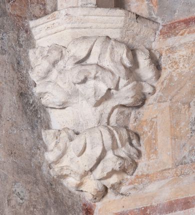 Zdjęcie nr 17: Zachowana dekoracja malarska znajduje się w tzw. starej zakrystii, określanej także jako oratorium królewskie. Dobudowano ją od północy do prezbiterium niepołomickiego kościoła. Jest to niewielka budowla na rzucie wydłużonego prostokąta, nakryta trójprzęsłowym krzyżowo-żebrowym sklepieniem, od wschodu zamknięta dwubocznie. Od zachodu w narożniku południowym widoczne jest załamanie muru, tworzącego dwie ściany wieżyczki schodowej. Do jej wnętrza prowadzi ostrołukowy portal. Oratorium oświetlają trzy ostrołukowe okna. Tylko czwarte, obecnie zamurowane, przeprute w murze północno-wschodnim pochodzi z czasów budowy kościoła. Stara zakrystia połączona jest z kościołem za pomocą ostrołukowego, profilowanego kamiennego portalu umieszczonego w środkowym przęśle ściany południowej. Na sklepieniu znajdują się rzeźbione zworniki z przedstawieniem w przęśle wschodnim głowy Chrystusa w nimbie krzyżowym, w środkowym maski liściastej, a w zachodnim motywów roślinnych. Podobnie rzeźbione motywy roślinne  pokrywają wsporniki, na które spływają żebra. 
Zachowana polichromia tworzy z architekturą starej zakrystii harmonijną całość. Białe wysklepki sklepień otoczone są wielobarwnymi, namalowanymi wzdłuż żeber, iluzjonistyczno-geometrycznymi pasami imitującymi kamienne inkrustacje w typie "arte cosmatesca". Pierwotnie polichromowane były także same żebra oraz rzeźbione zworniki i wsporniki. Pionowym rytmom barwnych pasów przeciwstawiają się na ścianie wschodniej, południowej i zachodniej dwa poziome, iluzjonistyczne malowane fryzy. Górny, w odcieniach brązów jest szerszy i przypomina gzyms. Przebiega w połowie wysokości ścian, na poziomie wsporników. Poniżej znajduje się drugi, o połowę węższy, skomponowany z wielobarwnych geometrycznych rozet w rombowych polach. Fryzy wyznaczają trzy strefy dekoracji. Dolny pas uległ zniszczeniu za wyjątkiem niewielkiego fragmentu iluzjonistycznie malowanej konsolki na ścianie południowej. Dla strefy środkowej głównej tło stanowi niebieska barwa. Niestety oba te pasy obecnie są mocno uszkodzone. 
Pierwotnie pas środkowy ścian zajmowały naturalnej wielkości postacie kobiece, ujęte powyżej kolan. Z namalowanych dwunastu świętych do naszych czasów przetrwało sześć - w całości cztery (na ścianie wschodniej, południowej i zachodniej) oraz jedna bez głowy (ściana południowa) i jedna w połowie (ściana zachodnia). Są to jasno lub ciemnowłose młode kobiety, trzymające palmy męczeństwa. Ubrane są w suknie z narzuconymi płaszczami w kolorach żółtym, oliwkowym, różowym, liliowym, brązowym i błękitnym. Jedna z nich, wyobrażona ponad wejściem na klatkę schodową w wieżyczce, jest ukazana jako kobieta w podeszłym wieku z okrytą głową i dłońmi uniesionymi na wysokość piersi w geście orantki. Głowy męczennic i orantki okalają plastycznie, tłoczone w zaprawie nimby zdobione promieniami. Na niektórych głowach dziewic zachowały się ślady namalowanych brązową farbą koron o niskich sterczynach w kształcie heraldycznych lilii. 
W ścianie północno-wschodniej dwubocznego zamknięcia znajduje się obecnie zamurowane lancetowate, ostrołukowe okno z fragmentami polichromii w glifie okiennym. Pierwotnie tworzyło ją dziesięć czterolistnych obramowań wpisanych w romby, umieszczonych jeden nad drugim. Przedstawiono w nich w półpostaci aniołów z głowami otoczonymi nimbami. W dolnej części okno do  poziomu gotyckich wsporników otacza iluzjonistycznie malowana dekoracja utworzona z motywów kamiennych płyt.  
W górnej strefie oratorium wyobrażono cykl hagiograficzny, składający się z sześciu scen namalowanych w ostrołukowych polach, wyznaczonych łukami tarczowymi sklepień i ujętych w obramienia z plastycznie malowanych zębów. Ograniczający je od dołu, iluzjonistycznie malowany, jakby wystający gzyms nadaje przedstawieniom teatralną głębie. 
Na ścianie południowo-wschodniej przedstawiono bliżej niezidentyfikowaną scenę męczeństwa. Na tle ochrowo-żółtej architektury ukazano z lewej strony na pierwszym planie grupę  rycerzy, z których dwóch widocznych jest w całej postaci w średniowiecznych zbrojach stylizowanych na rzymskie, w hełmach i z ostrołukowymi tarczami trzymanymi w lewych rękach. Ich odzież ma kolor błękitny, granatowy, czerwony, fioletowy, cynobrowy. Rycerze lekko unoszą głowy w stronę półpostaci wychylającej się z okna loggi w górnej części architektury. Był to zapewne władca, dziś jego postać zachowała się tylko fragmentarycznie. Postać z okna wskazuje palcem na centralnie ukazany kocioł zawieszony pod arkadą, stanowiącą część architektury tła. Widoczna w nim jest w półpostaci jasnowłosa kobieta w białej sukni na ramiączkach z modlitewnie złożonymi rękami na piersi. Jej głowę otacza nimb. Kocioł wisi na haku za półokrągły uchwyt, pod nim pali się ognisko. Z prawej strony kotła widoczna jest fragmentarycznie zachowana postać rycerza w zbroi, który oburącz długim kijem miesza w kotle. 
Na prawo od sceny męczeństwa na ścianie południowej namalowano scenę określaną jako "przed władcą". W centrum przedstawienia na tle architektury wyobrażono tron z zasiadającym na nim władcą. Jest to brodaty mężczyzna ukazany z profilu z koroną na głowie, który w prawej dłoni unosi berło skierowane w stronę przyprowadzonej do niego kobiety. Tron i architektoniczne jego obramienie malowane jest w kolorach brązu i ochry. Jego zaplecek dekoruje zawieszona pasiasta tkanina. Ciemnowłosy władca ubrany jest w turkusową szatę z narzuconym na ramiona brązowym płaszczem. Za tronem z lewej strony stoi paź o kędzierzawej fryzurze wsparty na trzymanym ostrzem w dół mieczu. Stojąca przed władcą kobieta ubrana jest w czerwoną długą suknię. Ma jasne włosy, a jej głowę okala nimb. Ręce ma skrzyżowane i związane na wysokości pasa. Obok niej stoi inna postać także w długiej szacie, z uniesioną prawą dłonią. Za świętą widoczne są inne postacie, niestety skala zniszczenia malowidła uniemożliwia ich opis i identyfikację. 
Trzecie malowidło, usytuowane nad wejściem do oratorium, ukazuje scenę dysputyt. W centrum przedstawienia pod architektonicznym zadaszeniem w formie portyku lub altany o kasetonowym stropie, wspartym na dwóch czworobocznych filarach, ukazano widoczne z profilu trzy siedzące  kobiety. Jedna z lewej strony a dwie naprzeciwko z prawej. Kobieta z lewej  ma odkryte jasne, długie włosy. Jej głowę otacza nimb. Na wysokość piersi unosi obie dłonie, sprawiając wrażenie, jakby w nich trzymała owalny przedmiot. Ubrana jest w ciemnoczerwoną długą suknię, zakrywającą nogi. Naprzeciw niej siedzą dwie inne niewiasty o długich, jasnych włosach w prostych koronach na głowach. Jedna z nich unosi swoją prawą rękę. Obie ubrane są w długie suknie w kolorze ochry. Za nimi pomiędzy filarami widoczna jest rozpięta zasłona w pionowe oliwkowe, zielone, białe i czerwone pasy. Na podłodze leży dywan dekorowany w żółte, zielone, niebieskie i czerwone pasy. 
Mocno zniszczone w dolnej części czwarte przedstawienie ilustruje scenę chłosty. Z lewej strony kompozycji wyobrażono budowlę z architektoniczną loggią, z której w półpostaci wychyla się władca. W prawej ręce poziomo trzyma berło skierowane w stronę grupy osób, za którymi wykonywana jest kara chłosty. Władca, podobnie jak w drugiej scenie, został ukazany jako mężczyzna o ciemnym zaroście i takich samych włosach. Na głowie ma koronę. Ubrany jest w brązowe szaty o różnych odcieniach. Centralnie przedstawioną stłoczoną grupę tworzy czterech żołnierzy oraz starszy mężczyzna w zawoju na głowie z siwą, długą brodą. Żołnierze mają zbroje i hełmy. Jeden z nich, najbliżej stojący z lewej przedstawiony został w profilu z głową i prawą ręką skierowaną w stronę króla. Także w stronę władcy zwrócony jest mężczyzna w zawoju na głowie z dwiema dłońmi uniesionymi na wysokość piersi. Z prawej strony kompozycji namalowano, dziś fragmentarycznie zachowany, rodzaj drewnianej szubienicy, utworzonej z poprzecznie zawieszonego na drewnianych podporach drążka. Nad dróżką do góry nogami wisi postać (dziś zniszczona), z której zachowały się jedynie stopy związane w kostkach sznurem. W jej stronę zwraca się jeden z żołnierzy ze środkowej grupy. Po prawej stronie szubienicy widoczna jest część postaci oprawcy, z której zachował się tylko fragment głowy oraz uniesiona lewa ręka z drewnianą pałką. 
Dwie ostatnie sceny umieszczono na zachodnim murze oratorium. Pierwsza z nich przedstawia strącenie bożka i została połączona z drugą ukazującą uwolnienia z więzienia. Część centralną kompozycji stanowi potrzaskana, wywracająca się kolumna, z której spada szatan w postaci żywego demona pokrytego sierścią. Strącił go widoczny w półpostaci w górnej części malowidła anioł trzymający w prawej ręce miecz. Z lewej strony kompozycji  klęczy na skalistej ziemi święta ubrana w długą ciemnoczerwoną suknię. Niestety nie zachowała się górna część jej postaci. Za nią stoi stłoczona grupa przerażonych świadków tego wydarzenia. Natomiast z prawej strony malowidła wyobrażono scenę uwolnienia z więzienia. Jej zasadniczym elementem jest architektoniczna struktura nawiązująca kształtem do wieży mieszkalnej, więzienia bądź bramy miejskiej. Święta ze związanymi rękami w ciemnoczerwonej sukni wychodzi z niej z prawej strony. W centrum budowli widoczne jest półokrągłe okno, a w nim zapewne jej popiersie o długich jasnych włosach, trzymające w dłoniach jakiś przedmiot. Wszystkie sceny cyklu w jedną całość wiąże gładkie niebieskie tło. Niezachowana kompozycja polichromii na ścianie północnej musiała odbiegać swym układem od pozostałych ścian. Płaszczyzna ścian została podzielona za pomocą węższego dolnego fryzu na dwie strefy. Górną część najprawdopodobniej zajmowały duże postacie stojące (fragment jednej z nich zachował się w sąsiedztwie okna w ścianie północno-wschodniej). Pod fryzem w części dolnej najprawdopodobniej była namalowana iluzjonistycznie wisząca kotara.   
    




